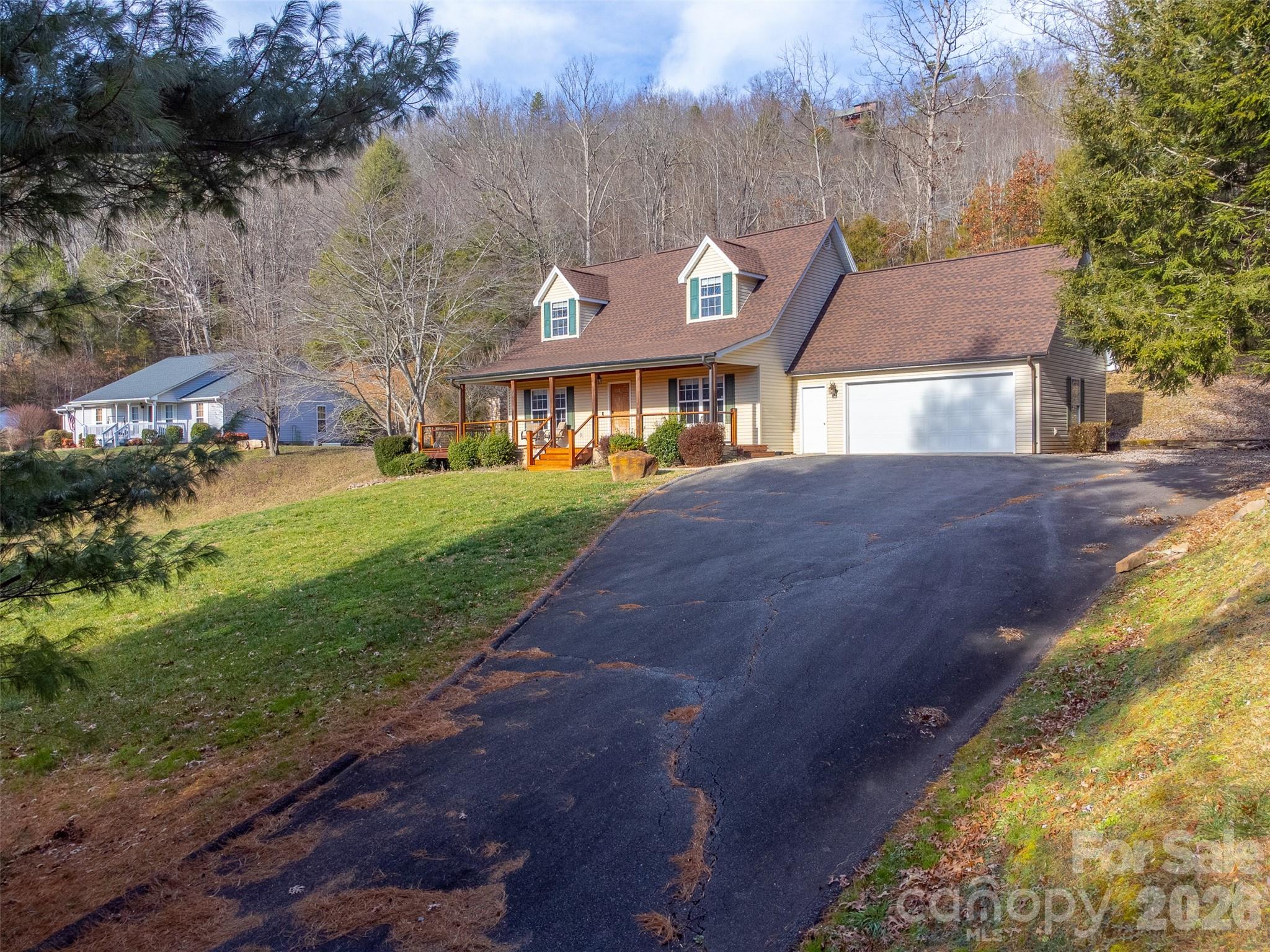Charming mountain home with gorgeous, long-range views! The exterior welcomes you with a long, paved driveway, charming covered front porch and spacious deck (complete with outdoor fireplace) - perfect for relaxing, entertaining, and taking in the view.  This well-kept 3 bed/2.5 bath home features an attached 2-car garage, comfortable living room with hardwood floors, abundant natural light and fireplace, plus an eat-in kitchen, and direct outdoor access. The primary bedroom with ensuite is on the main floor with additional beds and bath on the second floor. This warm, inviting property blends scenic surroundings with everyday functionality.