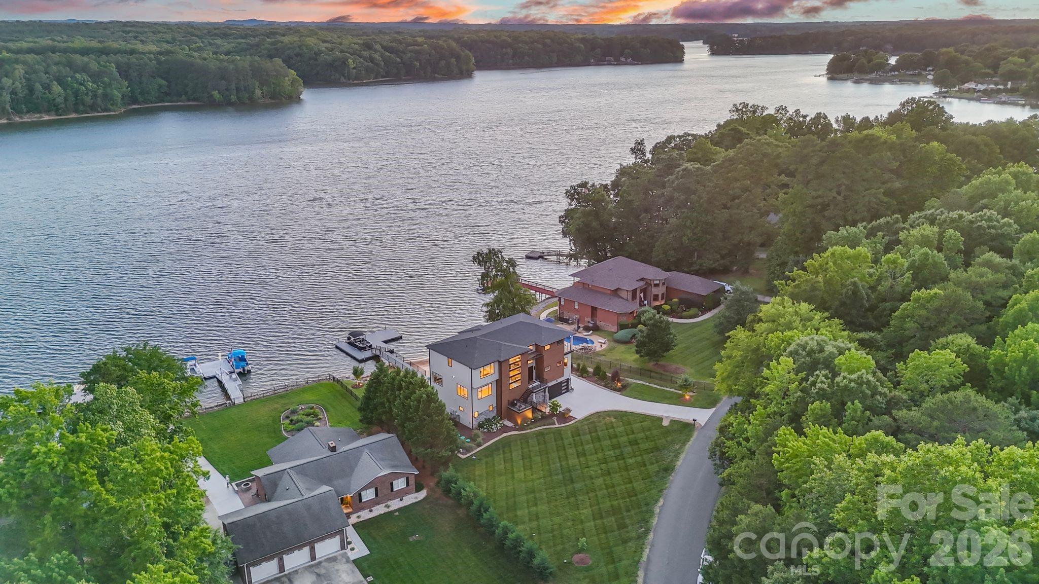 This NEXT LEVEL WATERFRONT Modern Pristine Luxury Estate w/ Contemporary Architecture comes w/ BREATHTAKING long range INFINITY WATER views & is located on High Rock Lake, North Carolina's 2nd largest lake with only a 50-60 min drive to Charlotte Douglas Airport! No expense spared in construction! You'll love the marble tiled kitchen, huge island and who doesn't want to surprise their friends with your LARGE HIDDEN PANTRY!? The luxurious primary suite offers a spa-inspired en-suite bath, while each of the home's three additional bedrooms also features its own private en-suite bath, ensuring exceptional comfort and privacy for family and guests!  You'll love the breathtaking sunsets, your private beach, your easy level walk to your oversized 1000+ sqft mega-dock, manicured yard with lush green striped grass, beautiful epoxy floor covered 3 car garage with storage to include an outlet ready to go for EV's & MORE!  Preapproved buyers are welcome!