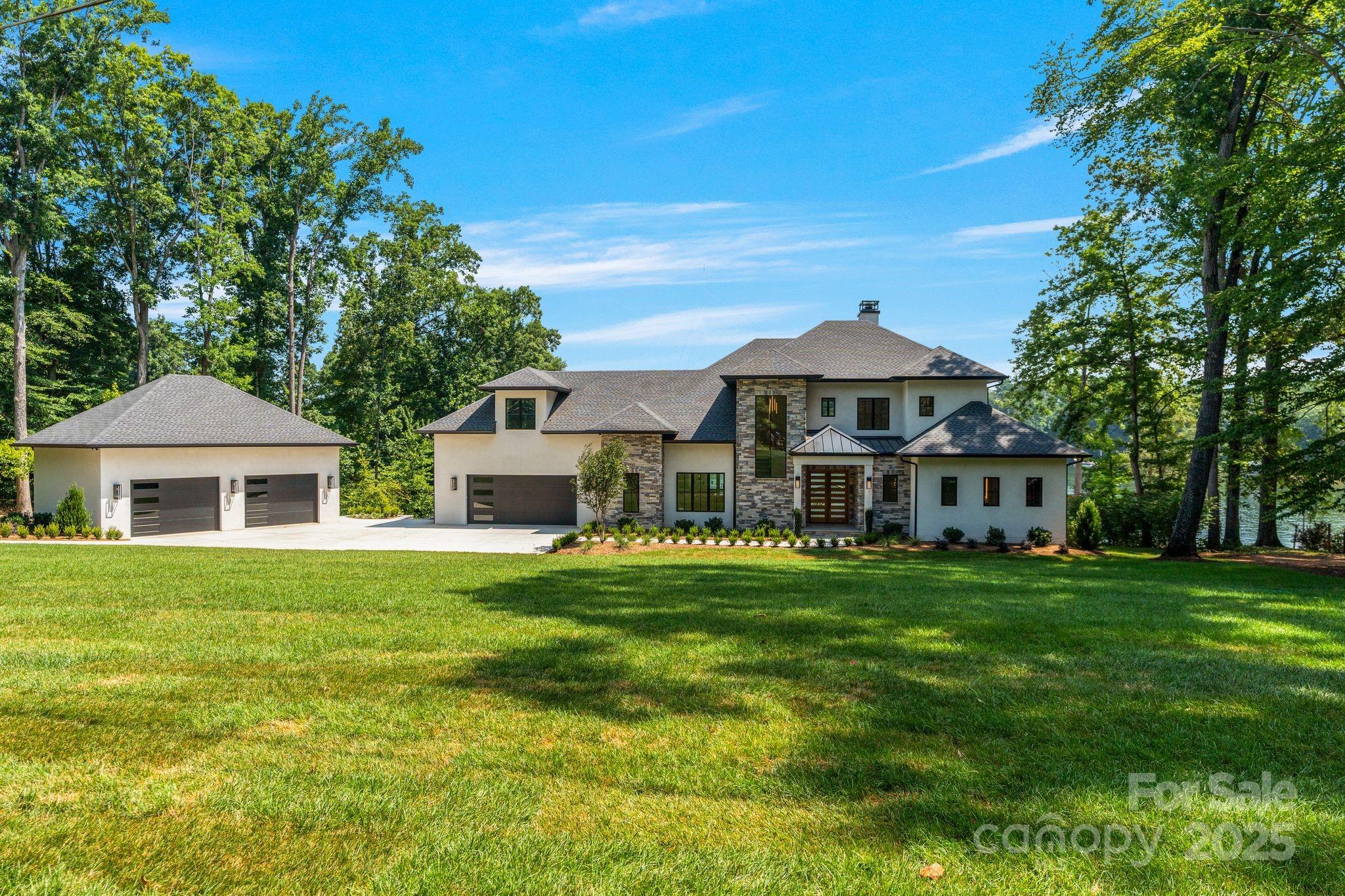 Experience elevated lakefront living in this new custom waterfront estate on Lake Norman, offering 160’+ of shoreline, a brand-new grandfathered 2-slip dock with sundeck, & deep-water access. Designed for luxury and lifestyle, this home features a main-level primary suite with spa-like bath, soaking tub, walk-in shower, dual vanities, & a custom closet. Triple slide glass doors in the great room open to a resort-style pool, spa, covered terrace with fireplace & infrared heaters, grilling station, & exterior-access pool bath. Inside, enjoy soaring ceilings, wide-plank wood floors, a dramatic stone fireplace, and a hidden scullery behind the chef’s kitchen with paneled appliances & massive island. Every bedroom features a private en-suite. Additional highlights include a bonus, office, rec room, designer millwork, & oversized attached garage w/ additional detached garage/workshop w/12' ceilings to accommodate a lift & half bath. A rare opportunity to own a turn-key, lakefront masterpiece