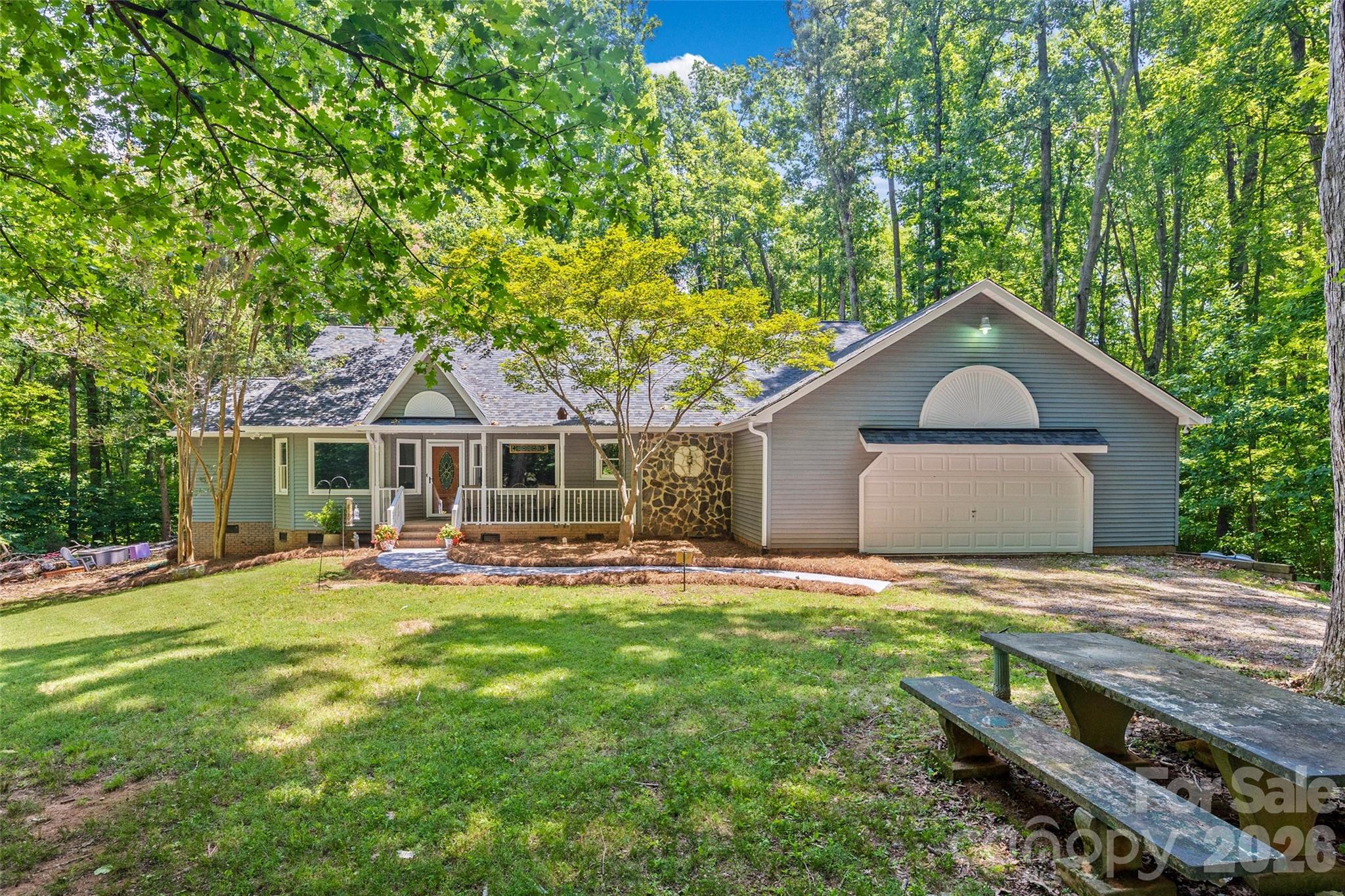 Tucked away on over six beautiful, wooded acres, where peace, privacy, and nature come together. This home offers a rare opportunity to enjoy secluded country living while still being within convenient reach of everyday amenities. From the moment you step inside, the home feels like a true sanctuary, centered around a large living room with vaulted ceilings, a cozy fireplace, and an expansive wall of windows that frame tranquil views of the mature trees and local wildlife. The main floor is designed for effortless living, featuring a massive primary suite that connects directly to the deck and includes its own private den, ideal for a home office or quiet reading room. It features a walk-in closet, dual vanities, whirlpool tub, and a separate tiled shower. Two additional bedrooms are located on the main level, while the upstairs offers two more large bedrooms, a full bath, and a clever plumbing hookup ready for a secondary laundry setup if desired. For the home chef, the kitchen is a standout space, beautifully updated with double ovens, a gas cooktop with a pot filler, a classic farm sink, and a comfortable breakfast area for casual mornings. Outdoor living is where this property truly shines. Step outside onto the expansive wraparound rear deck, with built-in seating and a gazebo where you'll be surrounded by tranquil views in every season. Whether enjoying your morning coffee, hosting gatherings, or simply unwinding at the end of the day, this outdoor living space offers year-round beauty and serenity. A separate 3-stall barn adds incredible versatility, offering endless possibilities for storage, hobbies, workshop space, equipment, or recreational use. Complete with a front porch, a generous 790 square foot attached garage, and new carpet, this retreat offers a special, secluded lifestyle you will love coming home to.