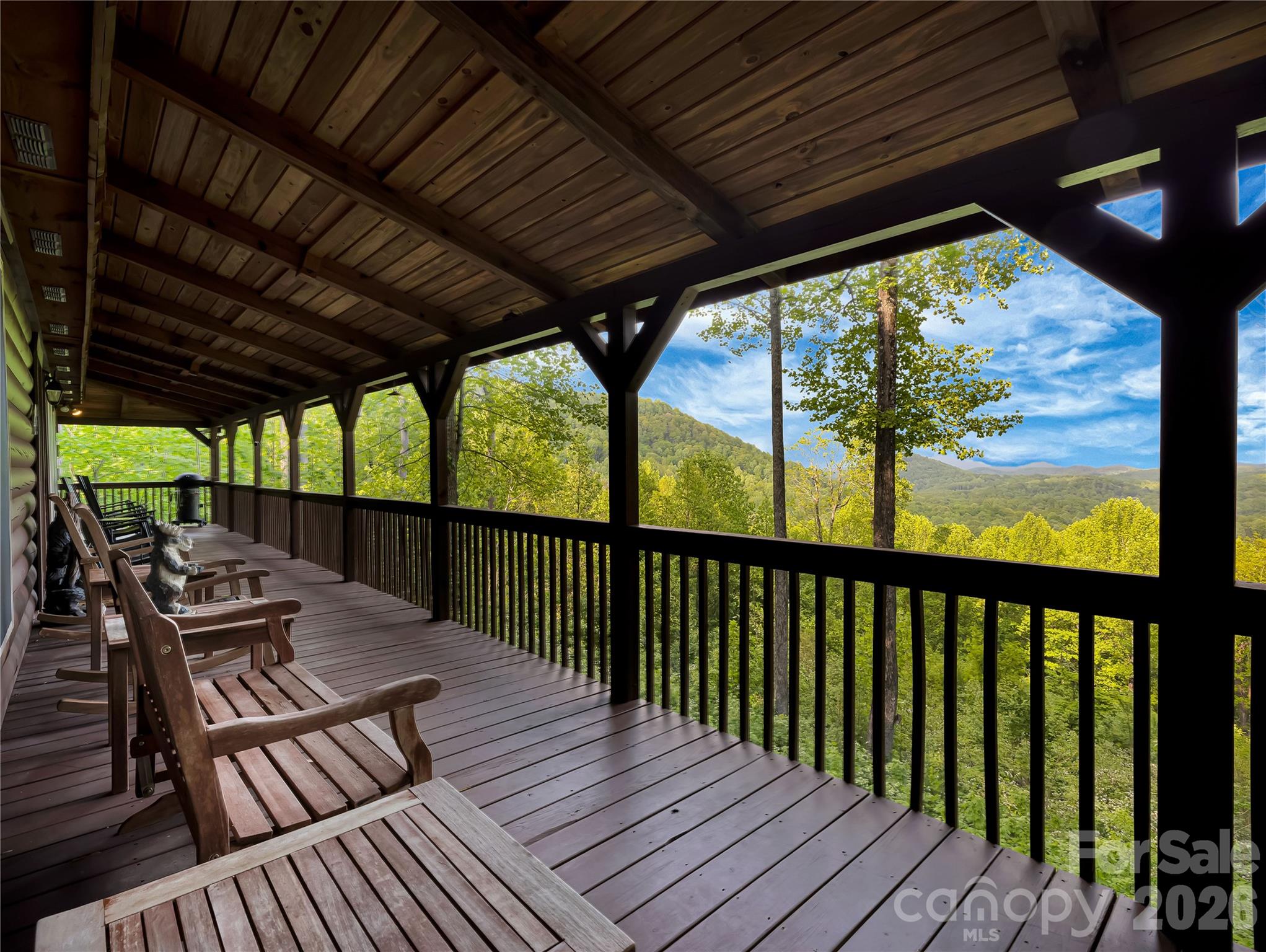 Welcome to 586 Tanglewood Lane, a quintessential mountain cabin tucked into the woods above the serene waters of Saluda’s Lake Sheila. Positioned at the edge of the 30,000-acre protected Greenville Watershed, this home offers a profound connection to the natural beauty of Western North Carolina while maintaining a comfortable proximity to neighbors. The property is designed for a versatile lifestyle that balances quiet mountain retreat with effortless entertaining.
Life here revolves around the peace of Lake Sheila, a non-motorized mountain lake that serves as a sanctuary for swimming, fishing, and paddling. This home makes the lake lifestyle easy, including a storage unit for your gear and toys and a designated spot at the community beach for your craft of choice. After a day on the lake, the massive wraparound porch provides the perfect setting for relaxation against a backdrop of breathtaking long-range Blue Ridge mountain views.
Inside, the open floor plan flows with a rustic elegance that lives exceptionally well. The great room is anchored by a classic wood burning fireplace, while the kitchen features a large island and breakfast bar with an additional sink, making it a natural gathering spot for guests. The primary suite is conveniently located on the main level and offers a private ensuite complete with a jet tub. An intentional design ensures that every bedroom in the home captures the majesty of the mountains, along with sparkling year-round views of Lake Sheila from the upper-level bedroom.

For quiet evenings in, the dedicated movie room comes fully equipped with a projector and screen. This property is offered as a truly turnkey opportunity, sold fully furnished at no extra charge. This includes the charming hand carved furniture and mountain bears that complete the cabin experience, allowing the next owner to move in and begin their story on day one.
Practical details are just as refined, with zoned HVAC and a one-car garage. The paved road access is a rare mountain luxury, making the drive easy even for sports cars and allowing for year-round travel. While you feel worlds away, you are just minutes from the historic charm of downtown Saluda and perfectly positioned for easy commutes to Greenville, Asheville, and beyond. This is more than a home; it is an invitation to experience the very best of the Saluda mountain lifestyle.