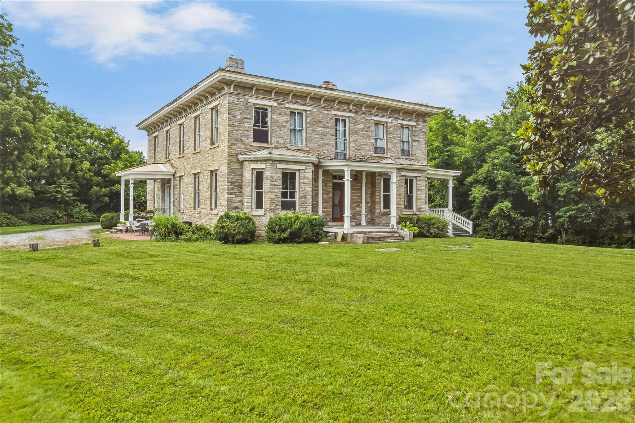 Perched on two picturesque acres in the heart of Fletcher, The Meadows is one of Western North Carolina's most remarkable historic residences—a rare opportunity to own a home whose story spans more than 160 years. Built in the late 1850's, this iconic stone estate is recognized on the National Register of Historic Places and has long been known as The Blake House, a landmark woven into the rich history of the Henderson County countryside. Constructed of locally quarried granite rubble stone in the distinguished Italianate style, the residence stands as a testament to enduring craftsmanship and architectural permanence. Its signature low hipped roof, substantial masonry construction, three interior chimneys, semi-hexagonal bay windows, and elegant front porch create a timeless silhouette unlike anything else in the region. Inside, nearly 6,000 square feet of living space offers the rare combination of historic character and generous scale. The Meadows traces its roots to the influential Blake family, whose legacy helped shape the development of this area throughout the nineteenth century. Opportunities to acquire a property of this caliber are exceptionally rare. With the home being around commercial buildings, there is opportunity to convert the home into a commercial space. With the 6 bedrooms upstairs, each could be converted into booths. The beauty of the home along with the parking lot would make for a great restaurant or potentially a Bed and Breakfast. The possibilities are endless. The Meadows is a living piece of North Carolina history—offering architectural significance, timeless beauty, and the privilege of becoming the next steward of one of Western North Carolina's most treasured residences.
