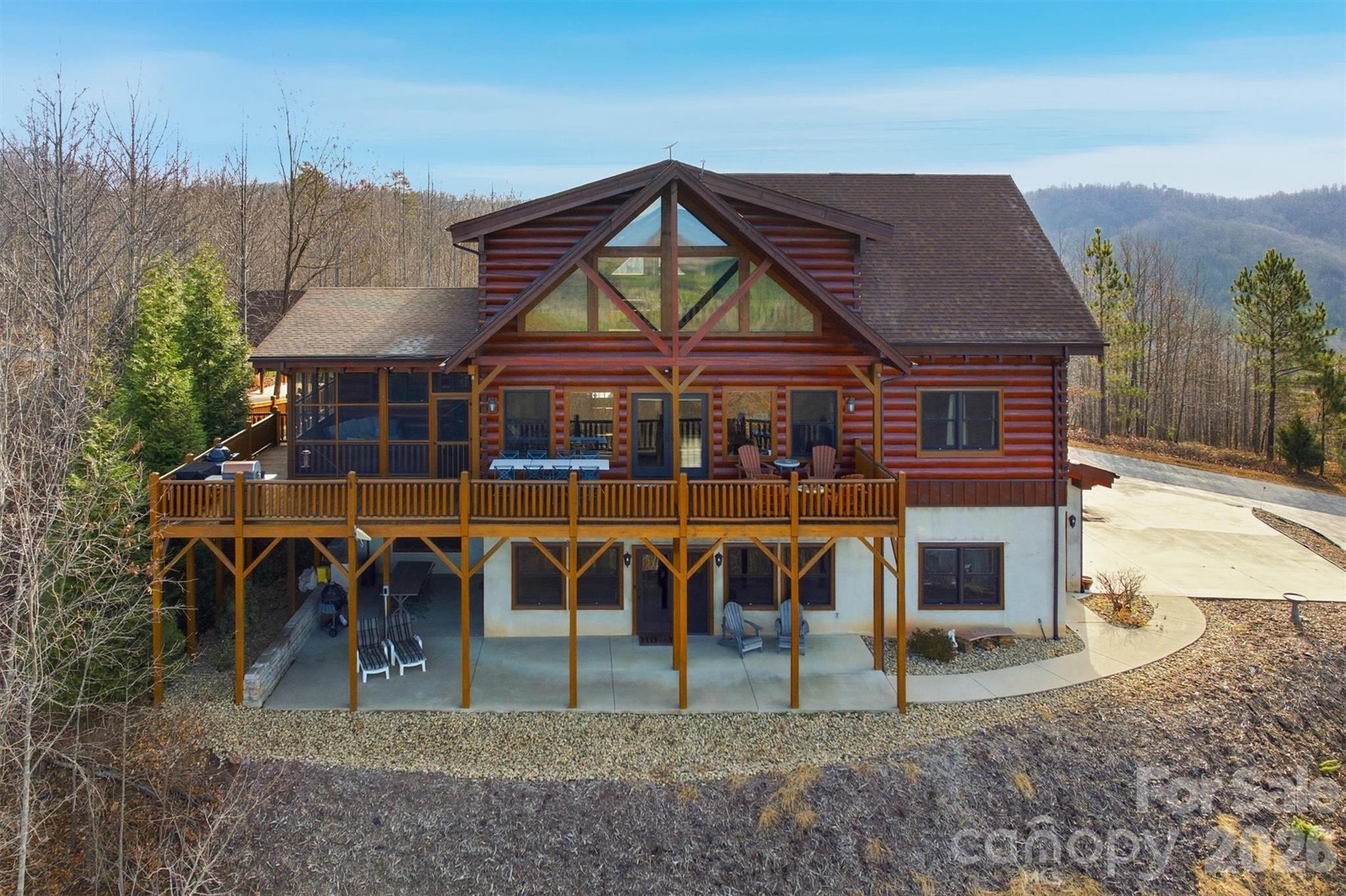 Welcome to your mountain sanctuary—where panoramic views meet modern luxury.
This custom-built three-story log home combines rustic charm with contemporary comfort, offering five bedrooms, six bathrooms, and an array of exceptional amenities. Whether you’re seeking a cozy retreat for two or the perfect gathering place for family and friends, this home delivers.
The main level showcases an open-concept living room, dining area, and chef’s kitchen, anchored by a soaring twenty-four-foot stone fireplace and floor-to-ceiling windows that frame breathtaking mountain views. The kitchen is a dream, featuring granite countertops, abundant cabinetry, two pantries, a wine cooler, two full ovens, a gas cooktop with telescoping exhaust, two dishwashers, and a wet bar—ideal for both everyday living and effortless entertaining.
The primary suite on the main floor offers stunning views, a spacious layout, and a spa-inspired en suite with a dual shower, multiple shower heads, and a jacuzzi bath with air jets perfectly positioned for soaking in the scenery. Upstairs, you’ll find two additional bedrooms with private or semi-private baths, along with a versatile loft space that works beautifully as a home office, playroom, or reading nook.
The lower level features a full in-law suite with two bedrooms, two bathrooms, a living area, kitchen, and its own laundry—perfect for multi-generational living or long-term guests. Entertainment and relaxation continue throughout the home, with a dedicated theater and recreation room, warm wood walls that create a true lodge-like atmosphere, and multiple living areas designed for both intimate evenings and large celebrations.
Outdoor living shines with a heated, screened-in deck, large fenced garden beds, and multiple covered seating areas. A wired, climate-controlled workshop with a man cave corner provides the perfect space for hobbies, projects, or unwinding, along with an additional workshop. Additional conveniences include dual laundry areas on the primary and lower levels, a garage, a carport, an EV charging port, an emergency generator hookup with a manual transfer switch, an outside connection for a hot tub, and abundant built-in cabinetry for storage throughout. For those seeking a seamless move, the home is also available furnished. 
Set within a private gated community, this property offers access to miles of nature trails, a stocked lake with a sandy beach, canoeing, swimming, and picnicking. It also features a pavilion with a large stone fireplace that serves as the heart of neighborhood events.
This home is the perfect blend of intimate comfort, expansive entertainment, income potential, fantastic craftsmanship, and additional features that you must see in person to appreciate fully. Schedule your private showing today and experience mountain living at its finest.