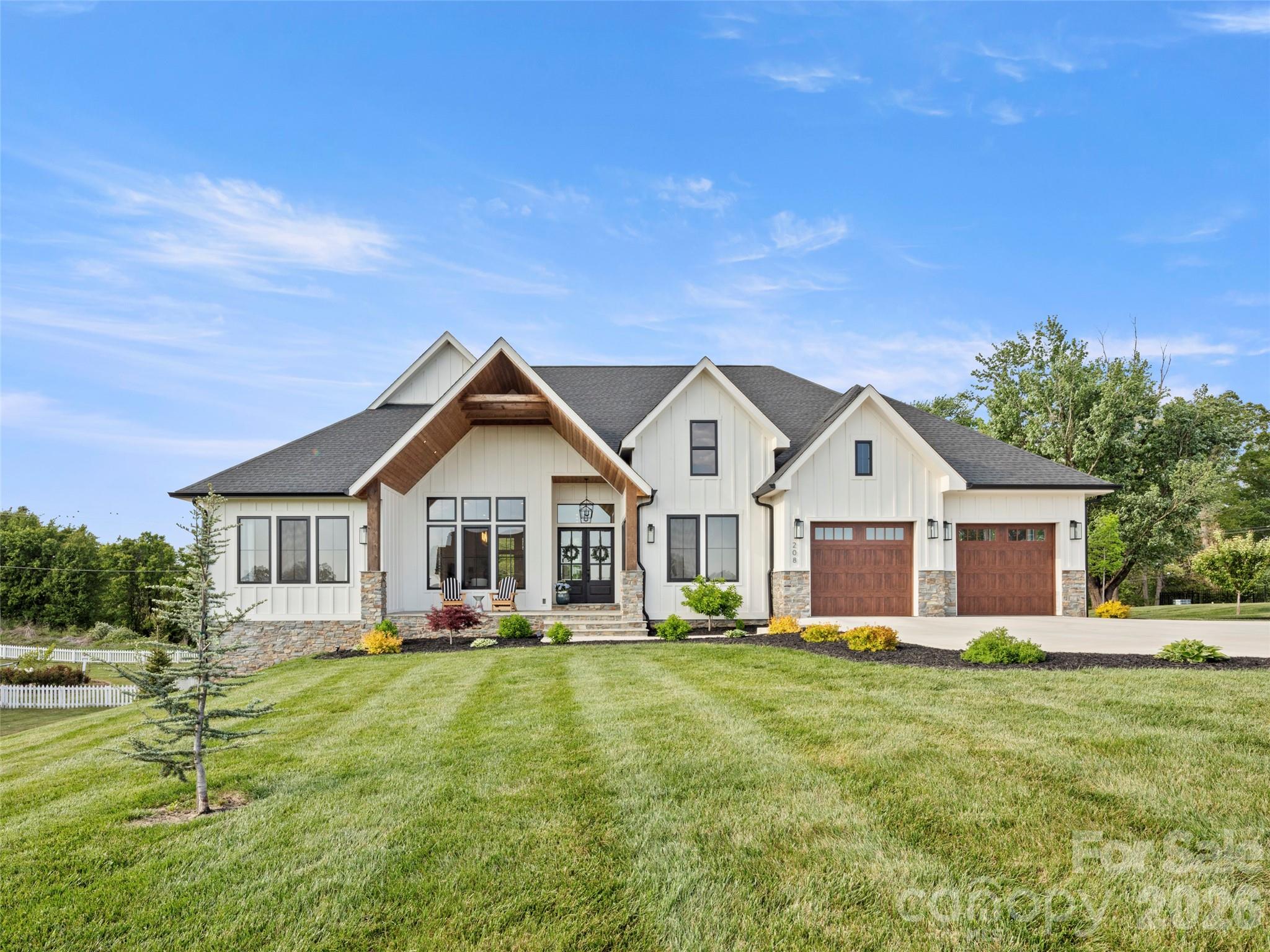 This exceptional luxury home blends modern design and impeccable craftsmanship. Shows like brand new in one of the area's most upscale communities. Surrounded by high-end custom homes, the neighborhood offers a walkable setting with scenic mountain views, tranquil ponds, and a welcoming community gathering area. The striking exterior showcases natural stone accents, a paver driveway, and a charming front sitting porch perfectly positioned to take in the mountain views. Outdoor living continues on the expansive covered back deck, complete with a beautiful tongue-and-groove wood ceiling and a built-in outdoor kitchen featuring a premium stainless steel grill, and a large, flat backyard for recreation or relaxation. Inside, the home features high-end finishes and thoughtful details throughout. The open-concept living area is flooded with natural light from premium European doors and windows, and anchored by a soaring natural gas fireplace with custom built-in cabinetry. Beautiful engineered oak wood flooring flows seamlessly throughout the main living spaces. The chef's kitchen is truly a showpiece, featuring premium luxury appliances, an oversized waterfall island, a pot filler, and a dedicated coffee station with an undercounter beverage refrigerator. A large, custom walk-in pantry provides exceptional storage and organization. The spacious primary suite offers a private retreat with a spa-like bath that includes a soaking tub and a large, glass walk-in shower. Both guest bedrooms are en-suites, each featuring a custom walk-in closet, offering comfort and privacy.
