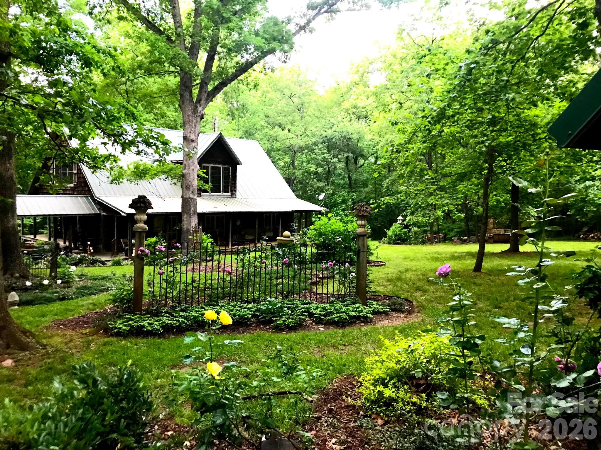 Welcome to the most majestic home that rests on a secret garden like 12.27 acres.This custom built house was carefully precured with the highest quality,one of a kind finishes.Your senses will delight in over 20 years of curated landscape including a mature magnolia grove that lines the exquisite private entrance,lavender roses,yellow azeleas,hydrangeas hugging a peaceful creek and so much more.Entering the gates you pass through a portal like magic.The charming home sits back with no  neighbors in sight.The entire property is fully fenced.Privacy and beauty set the theme.The house presents an authentic vintage style with a sweeping front porch that wraps around to a detailed back porch,displaying 4 antique french screened doors.Inside and outside living become one.When entering the home, the incredible kitchen with double XL refrigerators,double oven,custom light fixtures and a one of a kind antique island will take your breath away.Mature light fills the home with a soaring 21.8 foot main room ceiling and custom windows. There you can open the 4 french doors and enjoy the outside splendor from the comfort of your sofa,while relaxing by the fireplace.On the main floor is the cozy primary bedroom that boasts a beautiful bathroom.The walk in shower,antique claw foot soaking tub and large windows feel like a retreat.The main floor also features an open dining area twinkling with soft light from the antique chandelier,hardwood floors throughout,office,pantry and a half bath for guests.Upstairs you enter the scenic loft featuring a large bedroom across from a twin bonus room. The upstairs bathroom features another antique claw foot soaking tub and antique sink.The loft is stunning as it looks out of the large windows and sky high ceiling,truly setting the view apart from anything ordinary. All windows and french doors are covered in 3.5" high end shutters.The exterior is a combination of ceder shake plank and a warm field mossy patina metal roof inspired by surrounding nature.Attached to the home is a large cedar carport,with a tongue and grove ceiling accompanied by fans for those warm days.Two structures sit beside the round about. One can be used as a garage and both are also custom cedar.Hidden in plain sight the home provides a peaceful sanctuary among a secluded forest oasis.Lush pastures would be wonderful for horses.Bring your dreams and find your solitude in this one of a kind,once in a lifetime,enchanted house and wondrous garden.