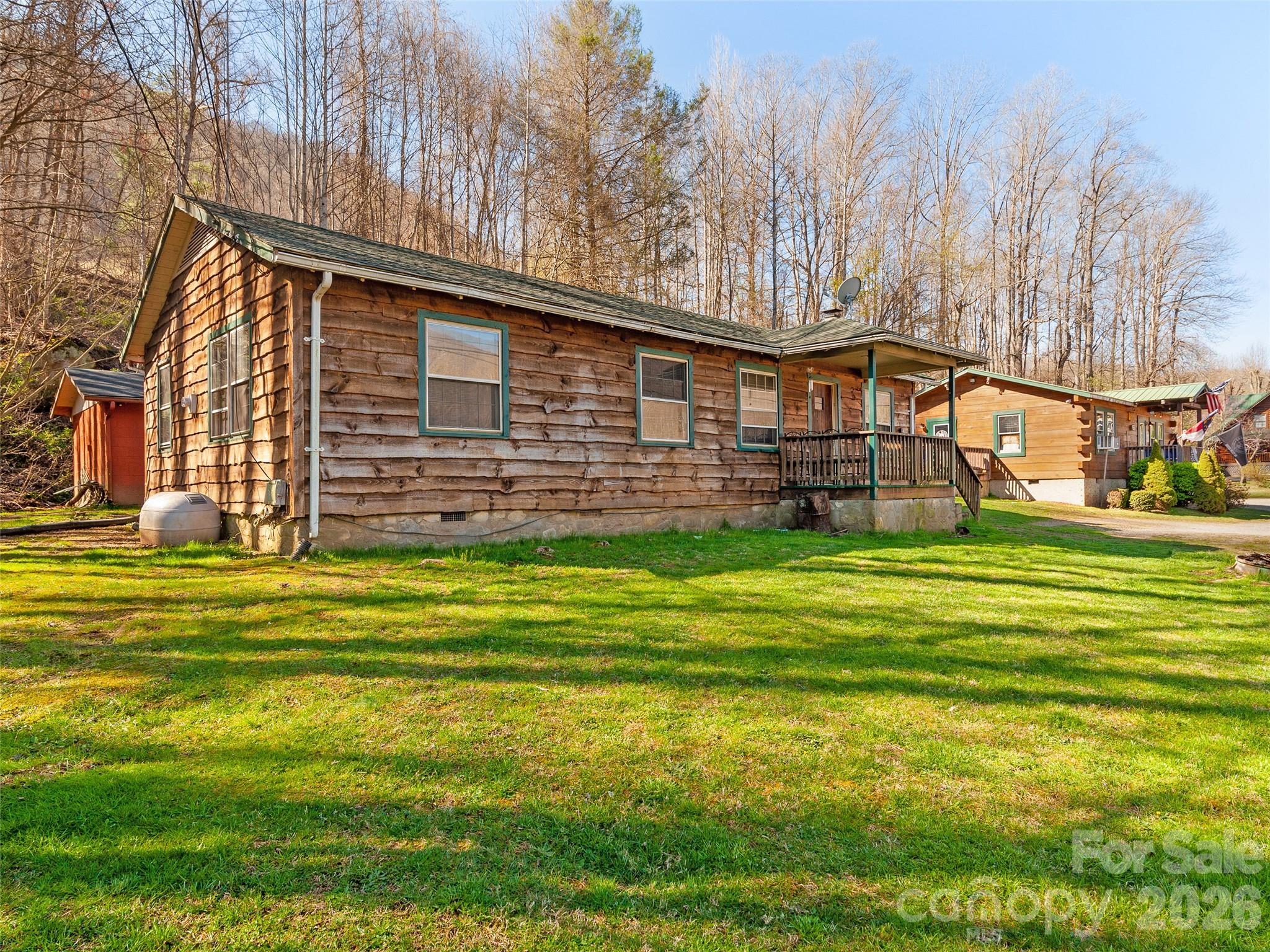 Discover this inviting 3-bedroom, 1-bath cabin on scenic Soco Road in Maggie Valley, NC, ideal for a permanent residence, vacation getaway, or short/long-term rental. Nestled in the Smoky Mountains, it’s minutes from downtown Maggie Valley, Cherokee, and the Blue Ridge Parkway. The cozy living room features a wood-burning stove, perfect for mountain evenings. A spacious galley kitchen with updated appliances & ample storage makes cooking a breeze. Wood and laminate flooring add warmth throughout, while the three bedrooms offer flexibility for family or guests. The exterior wood siding, treated in 2022, ensures durability, and a 300 sq. ft. block outbuilding provides excellent storage or workshop space. The level lot is perfect for relaxing or entertaining, with easy access to hiking, skiing, and attractions like Cataloochee Ski Area. Ideal for investors, its prime location ensures strong rental demand, especially near Western Carolina University. Don’t miss this Smoky Mountain gem!