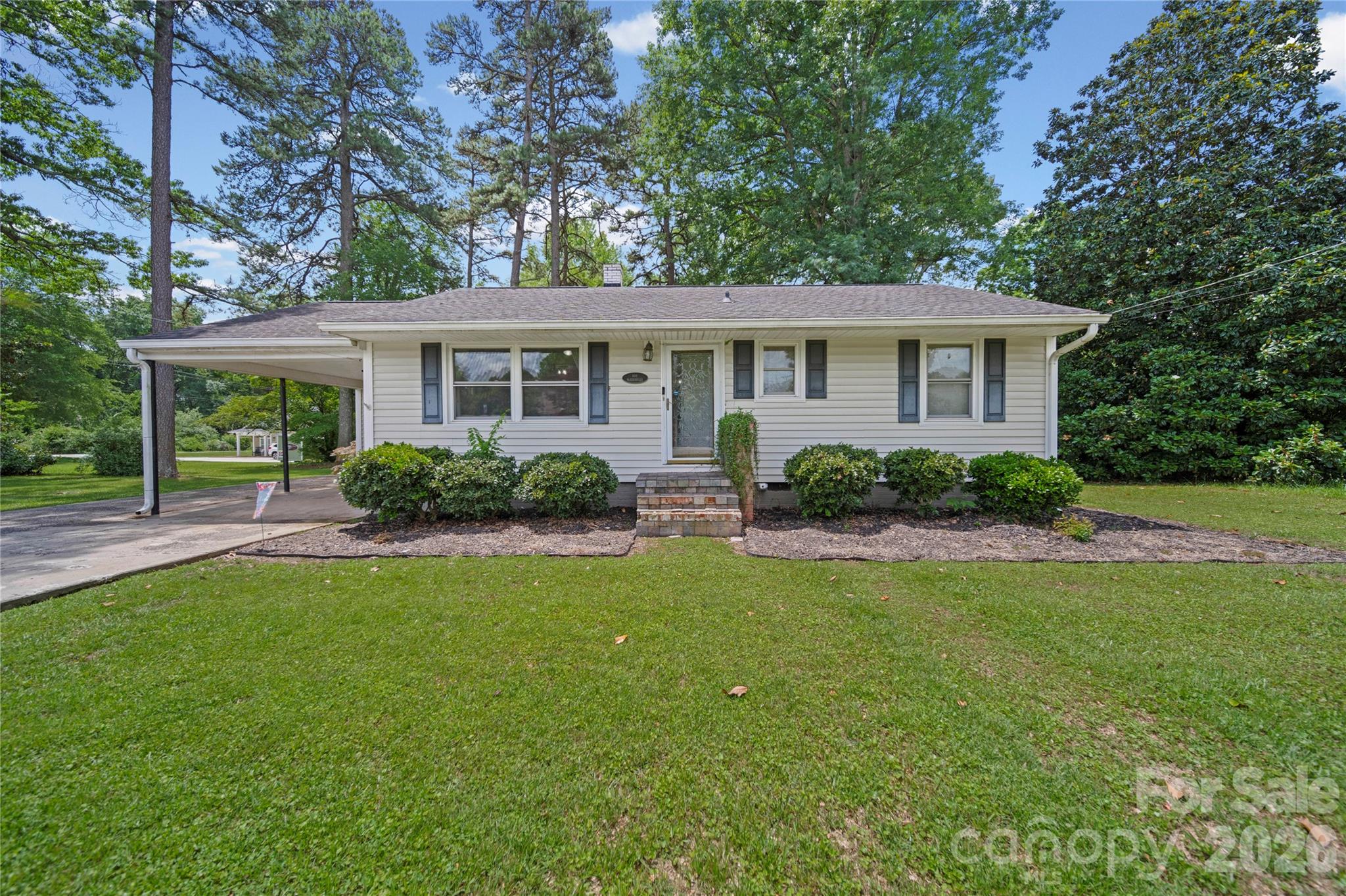 Welcome home to this charming 4 bedroom, 2 full bath ranch situated on over half an acre in Lowell.  Convenient to I-85, Uptown Charlotte, Belmont, Gastonia and the Airport, this beautifully maintained home features a farmhouse-style kitchen complete with quartz countertops, subway tile backsplash and a spacious peninsula perfect for gathering and entertaining.  The primary suite offers a relaxing retreat with a walk-in closet and cozy fireplace.  Outside, you will find a fenced in backyard featuring a deck and built-in fireplace ideal for entertaining or quiet evenings at home.  Additional highlights include a carport and shed, both offering extra storage space and dedicated workbench areas for hobbies, projects or organization.  With stylish updates, functional spaces and plenty of outdoor room to enjoy, this property offers the perfect blend of comfort and character.