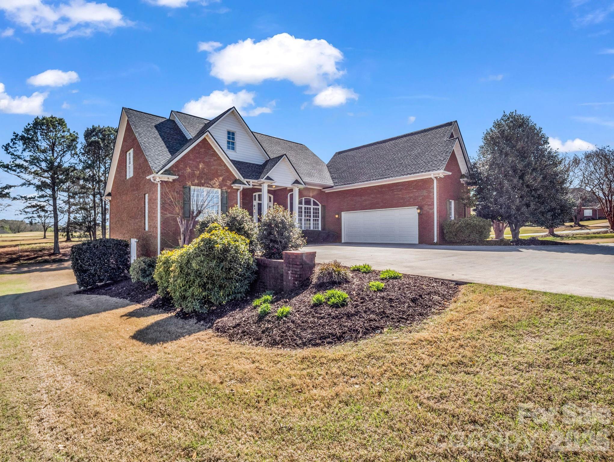 A Signature Golf Course Residence in Woodfin Ridge! Perfectly positioned along the 10th fairway of the prestigious Woodfin Ridge Golf Community, this stunning custom-built residence offers an exceptional blend of refined living, thoughtful design, and breathtaking golf course views. With almost 4,000 square feet of beautifully crafted living space, the home captures stunning golf course views from the back and mountain views from the welcoming front porch. This home is designed to elevate both everyday living and sophisticated entertaining.
From the moment you arrive, the circular driveway and charming brick paver front porch create a welcoming first impression. Inside, the home immediately impresses with soaring ceilings, abundant natural light, and an open, flowing floor plan designed for both everyday living and entertaining. The expansive great room serves as the heart of the home, featuring a gas log fireplace and dramatic ceiling height, while a balcony overlook from the second level adds architectural interest and enhances the home’s sense of openness and scale. The formal dining room, adorned with hardwood floors and intricate crown molding, offers a refined setting for memorable dinners and celebrations.  The well-appointed kitchen combines function and style with solid surface countertops, a smooth cooktop, breakfast bar, and spacious dining area designed for casual meals and effortless entertaining.
The main-level primary suite offers a peaceful retreat, complete with double closets and a spa-inspired bath featuring a jetted tub, dual vanities, and an updated tile shower. Upstairs you’ll find two spacious guest bedrooms and a shared hall bath, along with an additional 16 x 25 flex/bonus room that offers endless possibilities—perfect as a media room, playroom, home office, or additional guest space. The fully finished walk-out basement expands the home’s versatility with a spacious recreation room, bedroom, full bath, and additional flex space ideal for a private guest suite, in-law quarters, or teen retreat. Outdoor living is equally impressive. An expansive private deck overlooks the beautifully landscaped backyard and the rolling fairways beyond, offering the perfect setting for morning coffee, sunset views, or weekend gatherings. The backyard playset remains, adding to the home’s family-friendly appeal. Residents of Woodfin Ridge enjoy premier amenities including an 18-hole championship golf course, clubhouse, pool, tennis courts, playground, and on-site dining. Just minutes from Lake Bowen and with convenient access to I-26, I-85, shopping, schools, and regional airports, this location offers both tranquility and accessibility.  Luxury golf course living awaits in one of the Upstate’s most desirable communities.