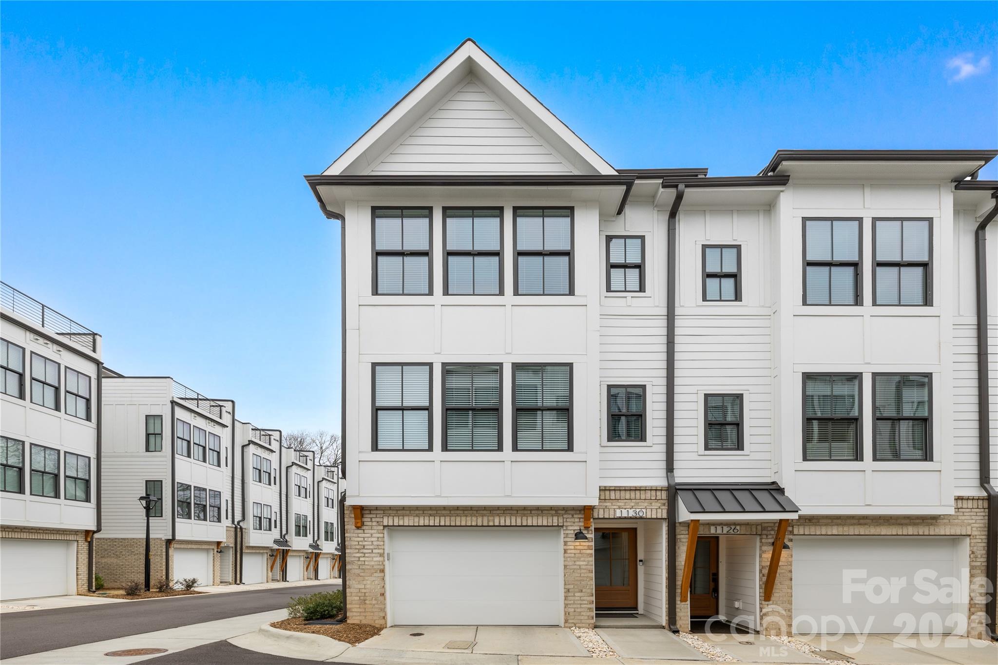 Modern end-unit townhome in a highly desirable Charlotte location with convenient proximity to Uptown, Optimist Hall, and Plaza Midwood's dining and entertainment scene. This light-filled 4 story home offers an open-concept. The main living level/2nd floor features wide-plank flooring, designer accent walls, and a kitchen fit for a chef featuring quartz countertops, stainless steel appliances, tile backsplash, a center island, and ample cabinet space that flow right into the dining area with its own private balcony or living room—ideal for hosting and everyday living. The spacious primary suite located on the 3rd floor offers natural light and a well-appointed en suite bath with dual vanities and a tiled walk-in shower. The second bedroom on this floor is complemented with a full private bath. Proceed to the 4th floor to enjoy outdoor living on the private rooftop terrace, perfect for relaxing or entertain your guests along the city skyline. With the third bedroom and half bath being located on this floor, this area can be optimized for flexibility to serve as a space for a office, workout room, or additional living space. The oversized garage on the 1st floor/main level provides extra storage and functional space. Located in a low-maintenance community with convenient access to shopping, dining, breweries, greenways, and major highways, this house offers a blend of modern style, comfort, and convenience.