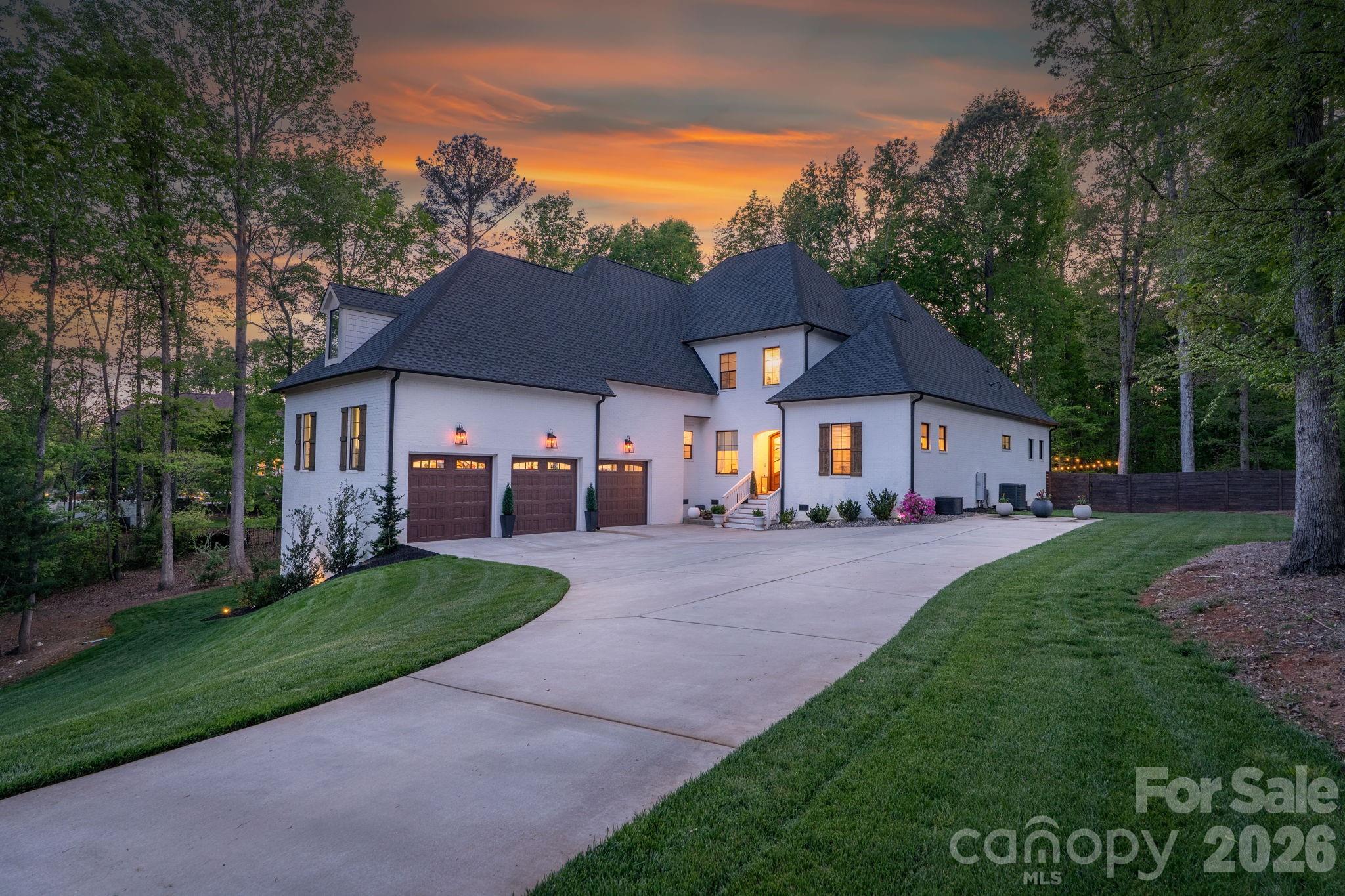 Welcome home to this stunning, custom French Provincial home offering refined design, modern comfort, and exceptional space. Situated on over an acre, luxury living meets peaceful surroundings near Lake Wylie in the beautiful community of Carolina Coves. Luxury abounds in the high-end finishes and custom design, making this home stand out. The main level includes a spacious primary suite and an additional bedroom, ideal for flexible living arrangements. Primary retreat features a gorgeous spa-like bathroom and custom closet for maximum relaxation and organization. The gourmet kitchen boasts a large island, walk-in pantry, and seamless flow into the dining area and inviting great room, complete with a cozy fireplace—perfect for hosting gatherings or relaxing evenings at home. Upstairs, you’ll find two additional bedrooms, each with their own private bathroom, and a generous bonus room which provides endless possibilities for a media room, home office, or playroom. The bonus room also features walk-in attic access for easily accessible storage space, or it could also be finished to create additional living space. The oversized 3-car garage will hold not only your cars, but also your lake toys, tools and additional storage space. Step outside to enjoy the beautifully landscaped and private fenced backyard and serene setting, offering the perfect backdrop for outdoor entertaining. You can relax on the covered back porch or step down onto the beautiful stamped concrete patio to enjoy this outdoor space. The property extends considerably beyond the current fence line, offering additional usable yard space with ample room for expanded outdoor living, including the possibility of a future pool. Lake Wylie access is just one mile away at Morningstar Marinas McLean. Lake life meets the perfect combination of refined features and comfort in this spectacular home. Zoned for the new Lake Wylie High School slated to open in August 2026.