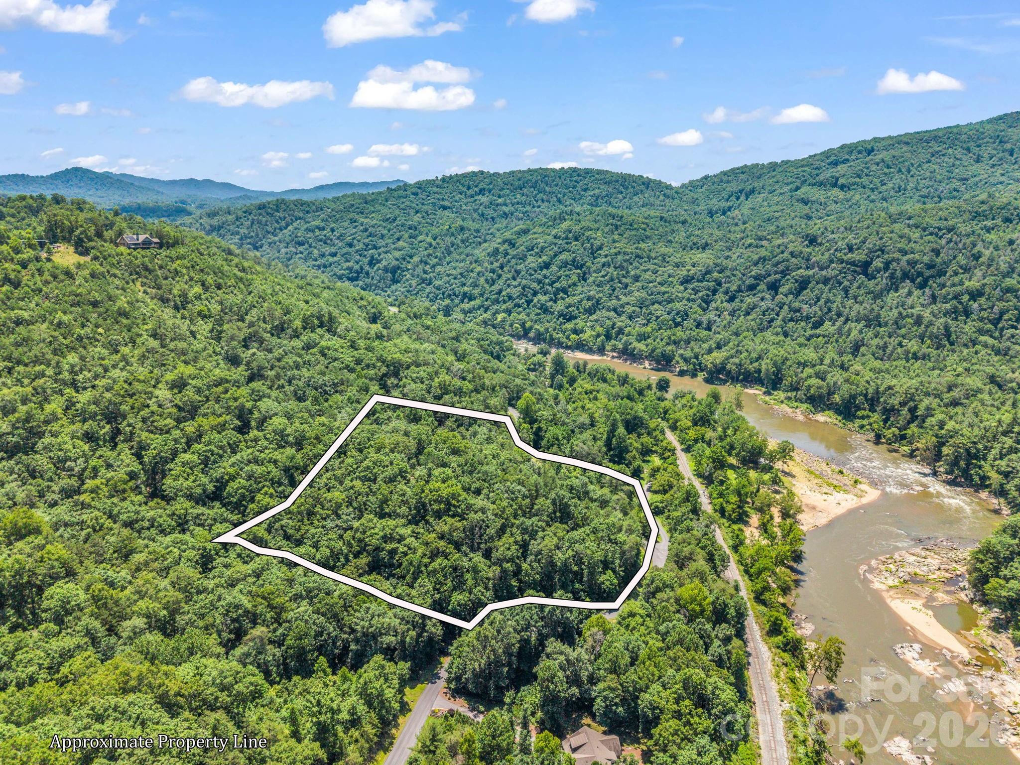 Estate-Quality Homesite on the French Broad River! Over 5 pristine acres await your dream home on one of the most coveted and LARGEST lots in this sought-after gated riverside community. The lay of this expansive lot is exceptionally suited for building, with a natural crest along the knoll of this 5 acres offering the perfect elevated homesite with long-range mountain views paired with river views below. Enjoy true privacy on all sides and an instant calming effect from the peaceful river sounds that bathe this property, a truly rare find in Western North Carolina! All this privacy within an exclusive gated community with access to some of North Carolina’s top tier amenities. Amenities include The River Lodge overlooking a turn in the French Broad River, featuring a fitness center, pool, and hot tub; River Park with direct access to the French Broad River; Tree House Park; and miles of hiking and ATV trails right outside your door. Fiber optic connectivity runs throughout the neighborhood, making remote work or streaming a breeze even in this peaceful mountain setting. Ideally located just 45 minutes to Asheville and 20 minutes to Marshall. An expired septic permit is on file and available upon request. Bring your builder and start planning your riverside retreat — this is estate living at its finest.