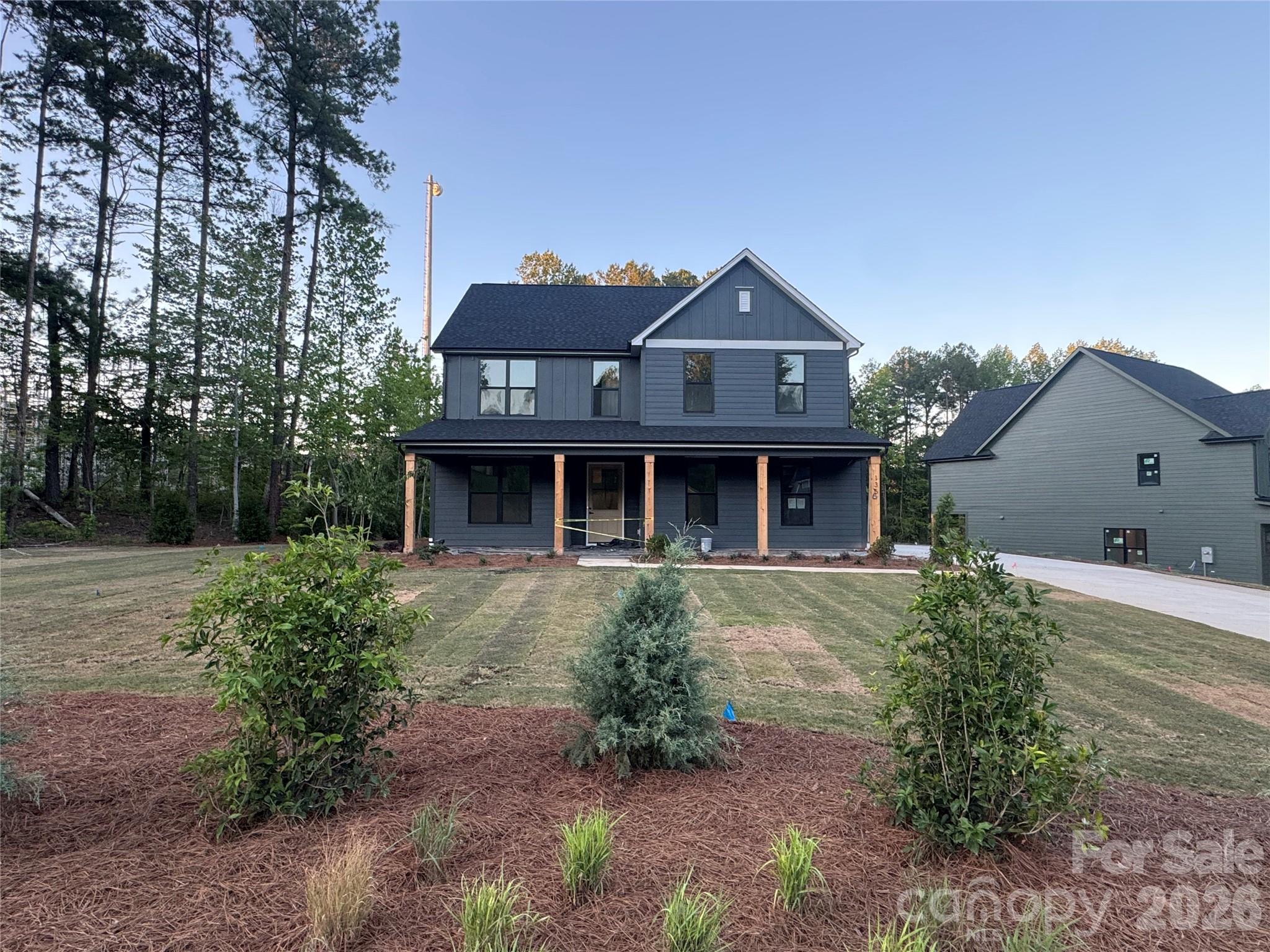 Welcome to 135 Parkdale Drive - a beautifully designed new construction home located approximately one mile from downtown Belmont, where you’ll enjoy local shops and dining.
Priced at $800,000, this five-bedroom, three-bath residence offers 2,726 square feet of thoughtfully crafted living space on a spacious 0.60-acre lot. The two-story Linden side-load model features striking James Hardie® Iron Gray siding, Rustic Black architectural shingles, black accents, cedar-wrapped columns, and a covered front porch that creates timeless modern farmhouse appeal. Inside, nine-foot ceilings, crown molding, Pure White walls, and natural White Oak hardwoods set the tone for a bright, inviting interior. The main level includes a guest bedroom and full bath, a private office with coffered ceiling detail, and a welcoming living room with a shiplap-accented fireplace. The kitchen is designed to impress with white shaker cabinetry, quartz countertops, a herringbone tile backsplash, matte black fixtures, and a KitchenAid appliance package. Upstairs, the vaulted primary suite with cedar beams connects to a spa-inspired bath featuring quartz countertops, brushed gold fixtures, and designer tile selections. With a side-load two-car garage, no HOA, and convenient access to Charlotte, Lake Wylie, and the airport, this home blends elevated finishes, functional design, and an unbeatable location.