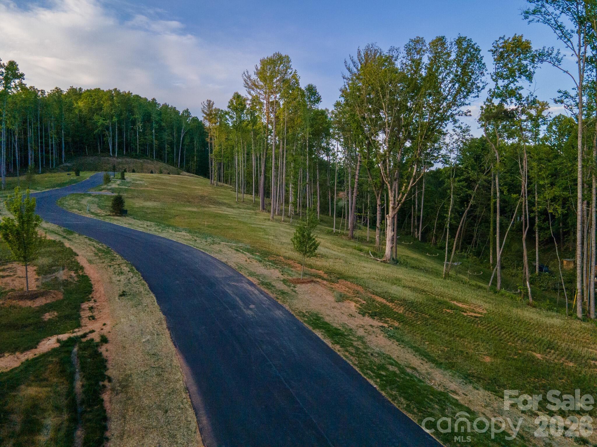 Homesite One at Harris Cove is a tree-framed parcel of about 0.94 acres bordering the community's shared open space, which lends a smaller lot the feel of something larger. Mature hardwoods remain across much of the property, private and settled from the first day, while southern exposure carries the homesite through long, light-filled mornings. The lot has already been pre-cleared and rough graded and is ready to build on as is, saving much of the early site work. It sits well off any public road, quiet by design. Harris Cove is a private, gated, eight-lot community off Irvine Drive in Fairview, NC, near Asheville, with a restaurant, brewery, ice cream parlor, and library a short distance away. It includes a private road, gated entry, street lighting, underground Duke Energy power, and shared StormTech stormwater, with well and septic per lot.

Every home is reviewed by an Architectural Review Committee; Tykke Homes is the preferred builder, and other qualified builders are welcome..