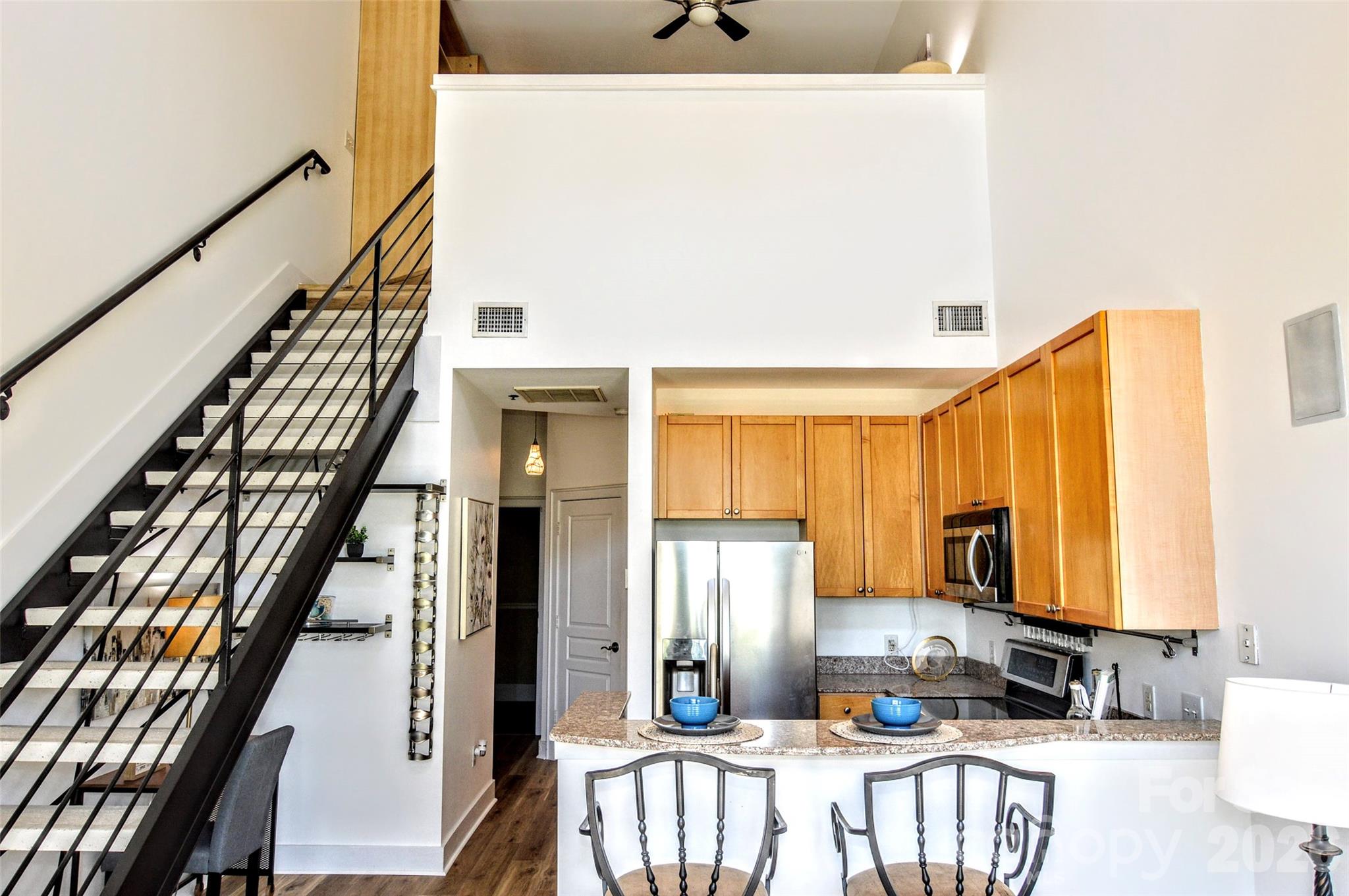 The ULTIMATE South End location! Just steps from the Rail Trail and some of Charlotte’s most popular restaurants and nightlife, this top-floor 1-bedroom, 1-bath condo offers the perfect blend of convenience and privacy.  Located on the 4th floor with easy access from the parking garage, this freshly updated unit features soaring ceilings and dramatic floor-to-ceiling windows that flood the space with natural light. The open-concept living area flows seamlessly into the kitchen, complete with wood cabinetry, stainless steel appliances, and a breakfast bar with stone countertops.  Enjoy your morning coffee or unwind in the evening on the private balcony overlooking vibrant South End activity.  The main level includes a welcoming foyer with a convenient storage closet, a laundry closet with brand new GE stackable washer and dryer, and a beautifully updated full bathroom featuring tile flooring, a stone countertop, a fresh vanity, and a modern backlit LED mirror.  Upstairs, the lofted bedroom offers a spacious built-in closet system designed for maximum organization.  Residents also enjoy access to a stunning rooftop terrace with unbeatable Uptown views—perfect for entertaining, working remotely, or simply relaxing.  Freshly painted and brand new flooring throughout, this move-in ready condo is a rare opportunity in one of Charlotte’s most sought-after locations. Don’t miss your chance at this great condo to work and live!