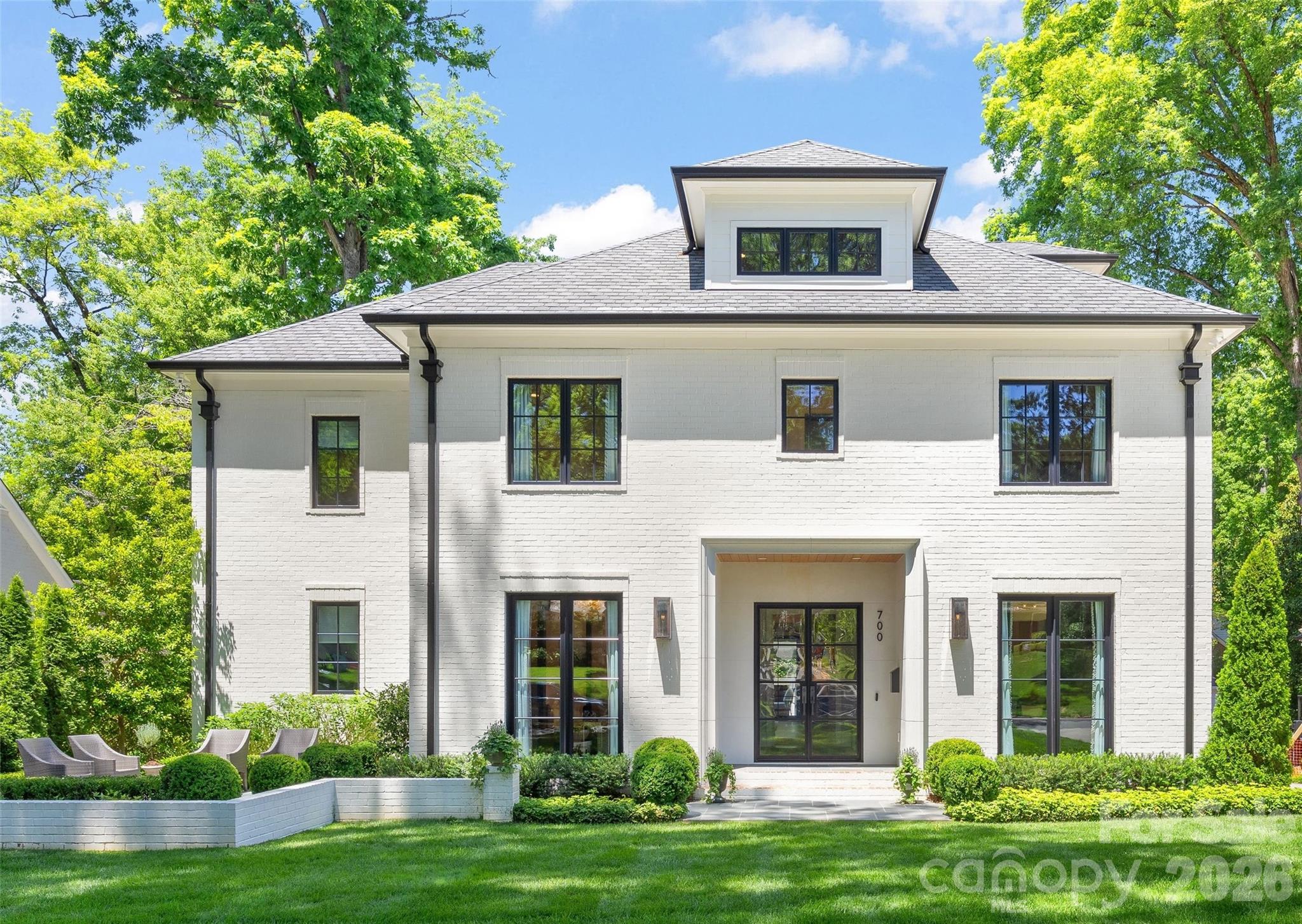 Stunning elevated brick residence built in 2020 in the heart of Eastover, offering 5 bedooms, 4.5 bathrooms, and over 5,600 sq/ft of refined living space on a beautifully landscaped lot. Thoughtfully designed with high ceilings, white oak hardwoods, gorgeous designer wallpaper and lighting, fresh paint, and exceptional indoor-outdoor living throughout. The chef’s kitchen features custom soft-close cabinetry, marble island, quartz perimeter surfaces, Thermador appliances, sunny breakfast niche, and adjoining scullery with wet bar, wine cooler, beverage center, and walk-in pantry. Stunning lounge and formal dining room are perfect for entertaining. The family room with coffered ceiling, cast stone fireplace, and large sliding doors opens seamlessly to the covered bluestone terrace with heaters, in-ceiling speakers, and fireplace, overlooking the flat rear yard with mature privacy landscaping. Main-level primary suite offers terrace access, custom closet with W/D hookup, and spa-like bath with soaking tub, zero-entry shower, heated  floors, and dual quartz vanities. Upper level features four secondary bedrooms with walk-in closets and en-suite bath access and large bonus room. Finished third-floor flex space plus massive walk-in attic provide incredible versatility and storage. Detached 2-car garage with epoxy flooring and unfinished future bonus space above. Exceptional Eastover location just moments from neighborhood schools, parks, and dining- luxury living at its finest!