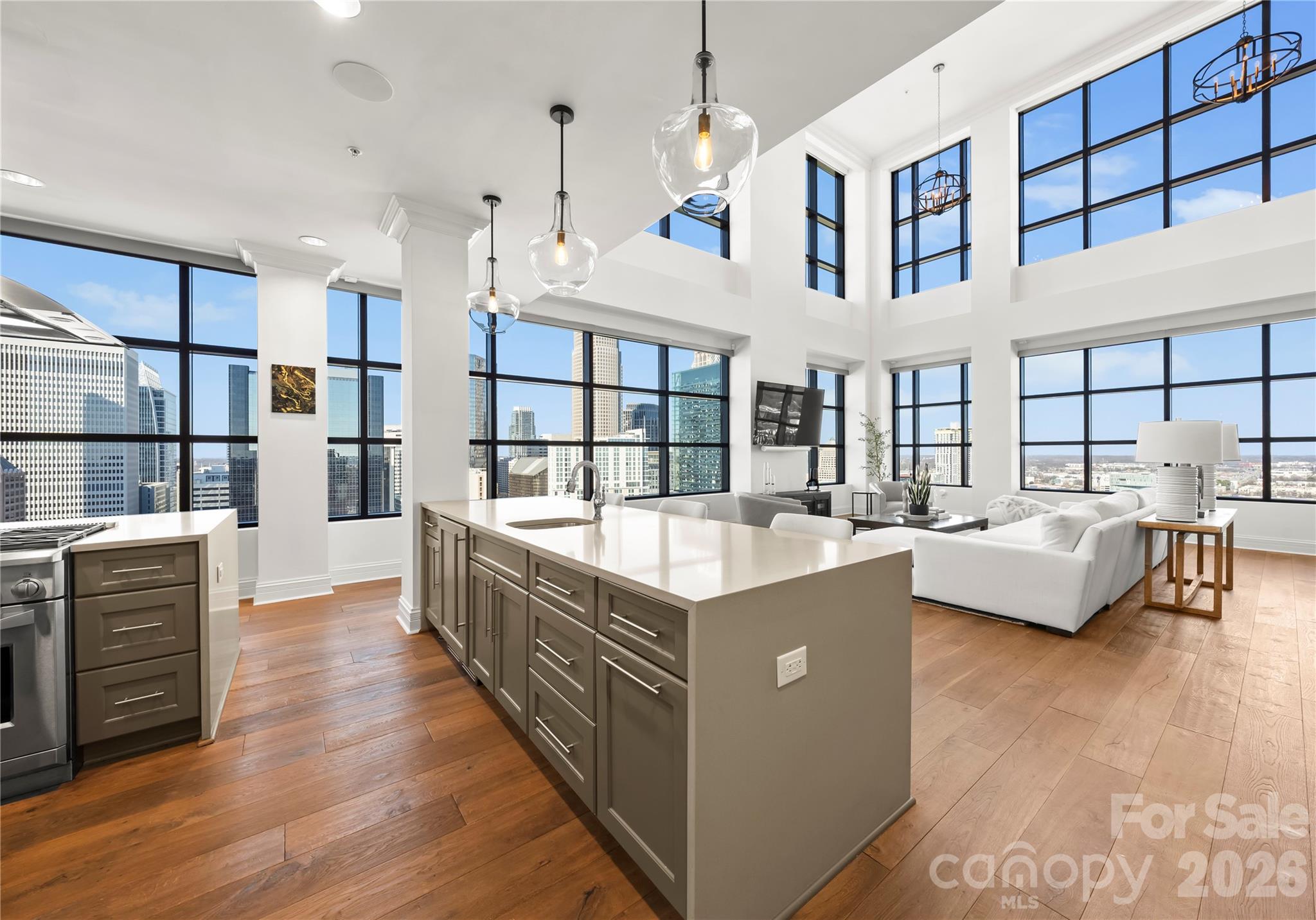 Rising high above the energy of Uptown Charlotte on the 22nd floor of the iconic SKYE Condominiums, Residence 2203 delivers a true “city-in-the-sky” lifestyle—where panoramic skyline views, walkable convenience, and luxury high-rise living converge in one unforgettable address. Spanning over 4,000 square feet across two levels, this expansive 3-bedroom, 3.5-bath residence lives like a penthouse, offering a rare blend of scale, architectural drama, and separation of spaces—complete with front-row views overlooking the Spectrum Center and Uptown’s most recognizable skyline corridors. From the moment you enter, the home’s presence is undeniable. A dramatic two-story living space framed by expansive windows brings the city into the room—bright and inspiring by day, and dazzling at night. The open-concept design flows seamlessly through the great room, dining area, and chef’s kitchen, creating an ideal setting for elevated entertaining and effortless everyday living. The kitchen is both beautiful and functional with gas cooking, stone surfaces, a generous center island, premium appliances, and custom cabinetry—anchored by a wet bar and wine refrigerator that elevate the entertaining experience whether you’re hosting a gathering or enjoying a quiet evening in. The main level offers flexible guest accommodations and well-appointed baths, while the upper level serves as a private retreat. An impressive primary suite is complemented by a loft that overlooks the dramatic living area below—enhancing the home’s vertical volume while offering privacy and a true sense of arrival. Balcony and terrace access extend the living experience outdoors, creating the perfect backdrop for morning coffee, sunset views, or pre-event evenings with the city lights sparkling below. SKYE is renowned for amenities that rival boutique hotels while maintaining a private residential feel—featuring a private rooftop terrace with pool and skyline views, an on-site rooftop restaurant (Fahrenheit) with dining high above the city, a fitness center with cardio and strength equipment, and resident spaces including a theater room, club room, and game room. Secure garage parking, controlled access, and building services complete the luxury high-rise experience. Location is everything—and SKYE’s South Caldwell Street address places you in the center of Uptown’s entertainment and cultural district. Spectrum Center is just steps away, while Bank of America Stadium, Truist Field, and the Charlotte Convention Center are all within easy walking distance. Enjoy quick access to some of Uptown’s favorite dining and nightlife destinations, including Fahrenheit (in-building), Coquette, Aria Tuscan Grill, and McCormick & Schmick’s, along with the Blumenthal Performing Arts Center and Uptown’s most active social scene. For frequent travelers, Charlotte Douglas International Airport is approximately 15–20 minutes away, offering seamless access for business and leisure. Two assigned parking spaces in the secured garage are included and transferable with the sale—an exceptional advantage in Uptown living.