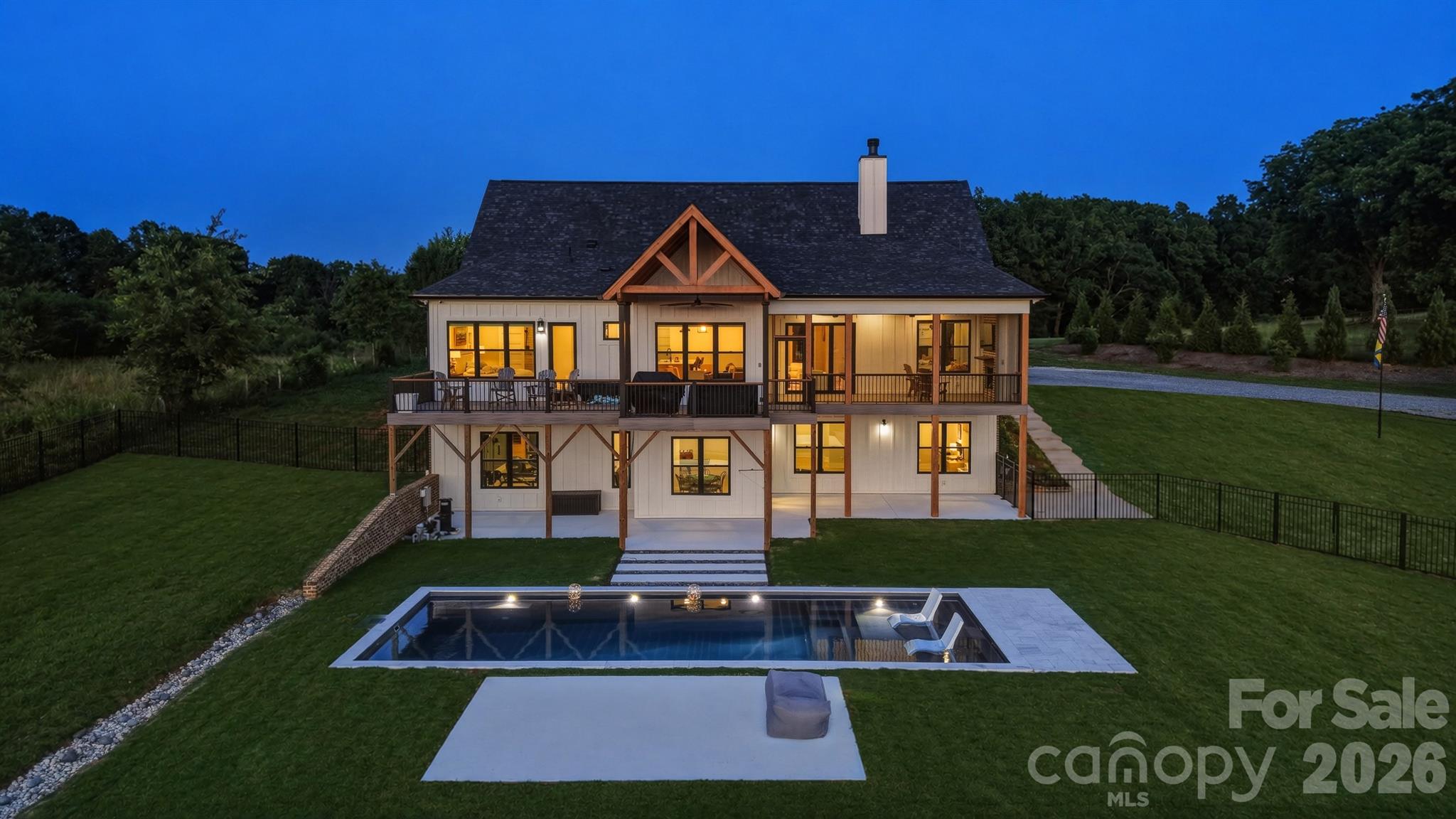 Experience luxury, privacy, and breathtaking year-round mountain views at this exceptional custom-built estate in the Mountain View area of Hickory. Completed in 2024 and situated on 11.28 fenced acres, this remarkable property offers 5,353 square feet of thoughtfully designed living space, a attached three-car garage, resort-style outdoor amenities, and spectacular sunset views.

A covered front porch welcomes you inside where French oak flooring, 10-foot ceilings, and an open floorplan create an impressive first impression. The great room serves as the heart of the home, featuring a stunning Texas limestone fireplace with a concrete mantel, built-in shelving, vaulted beamed ceilings, and expansive tri-fold glass doors that seamlessly connect indoor and outdoor living.

The gourmet kitchen is designed to impress with an oversized island offering storage and breakfast bar seating, a 48-inch dual gas range with six burners and griddle, pot filler, microwave drawer, double-decker dishwasher, and GE Café refrigerator with hot and cold water dispenser. A walk-in pantry elevates functionality with additional cabinetry, butcher block countertops, beverage refrigerator, and sink.

The dining area captures beautiful mountain and sunset views and opens directly to a partially covered deck complete with a gas stub for grilling. The adjoining screened porch creates an extraordinary outdoor living experience featuring composite flooring, Sonos speakers, built-in surround sound, recessed lighting, a gas fireplace, television, and panoramic views overlooking the saltwater pool, fenced pasture, and surrounding mountains.

The main-level primary suite offers a private retreat with views of the pool, pasture, mountains, and sunsets. Features include a coffered ceiling, electric fireplace, and Cat 6 hardwired internet connection. The luxurious ensuite bath showcases tile flooring, a soaking tub, tiled shower with rain head, quartz double vanity, linen closet, water closet, and walk-in closet with direct access to the laundry room complete with sink and dog-washing station. Two additional main-level bedrooms are positioned within a split-bedroom layout and share a full bath with tile flooring.

Upstairs, a spacious flex area leads to an additional bedroom and full bath featuring tile flooring, quartz vanity, and abundant storage.

The finished walkout basement expands the home's versatility with 10-foot ceilings, luxury vinyl plank flooring, a dedicated office with Cat 6 hardwired internet, full bath with walk-in tile shower, kitchenette with beverage refrigerator and commercial ice maker, exercise room with oversized glass doors and mirrored wall, and an impressive media room with surround sound, projector, and app-controlled lighting. French doors fully open to the covered patio and pool area, creating effortless indoor-outdoor entertaining.

Outside, a recently installed fiberglass saltwater pool with tanning ledge serves as the centerpiece of the backyard oasis. The property is fully fenced and includes fenced pasture areas, long-range mountain views, prewiring for landscape lighting, security cameras, ADT-protected entrances, hot and cold exterior water spigots, and screens on all operable windows.

Additional highlights include generator-ready capability, well filtration system, tankless water heater, hardwired internet and security hub, Cat 6 wiring throughout key spaces, and separate gas heat and central air systems serving each level.

This rare Mountain View estate offers luxury living, modern technology, extensive acreage, exceptional entertaining spaces, and unforgettable views—all within one extraordinary property.