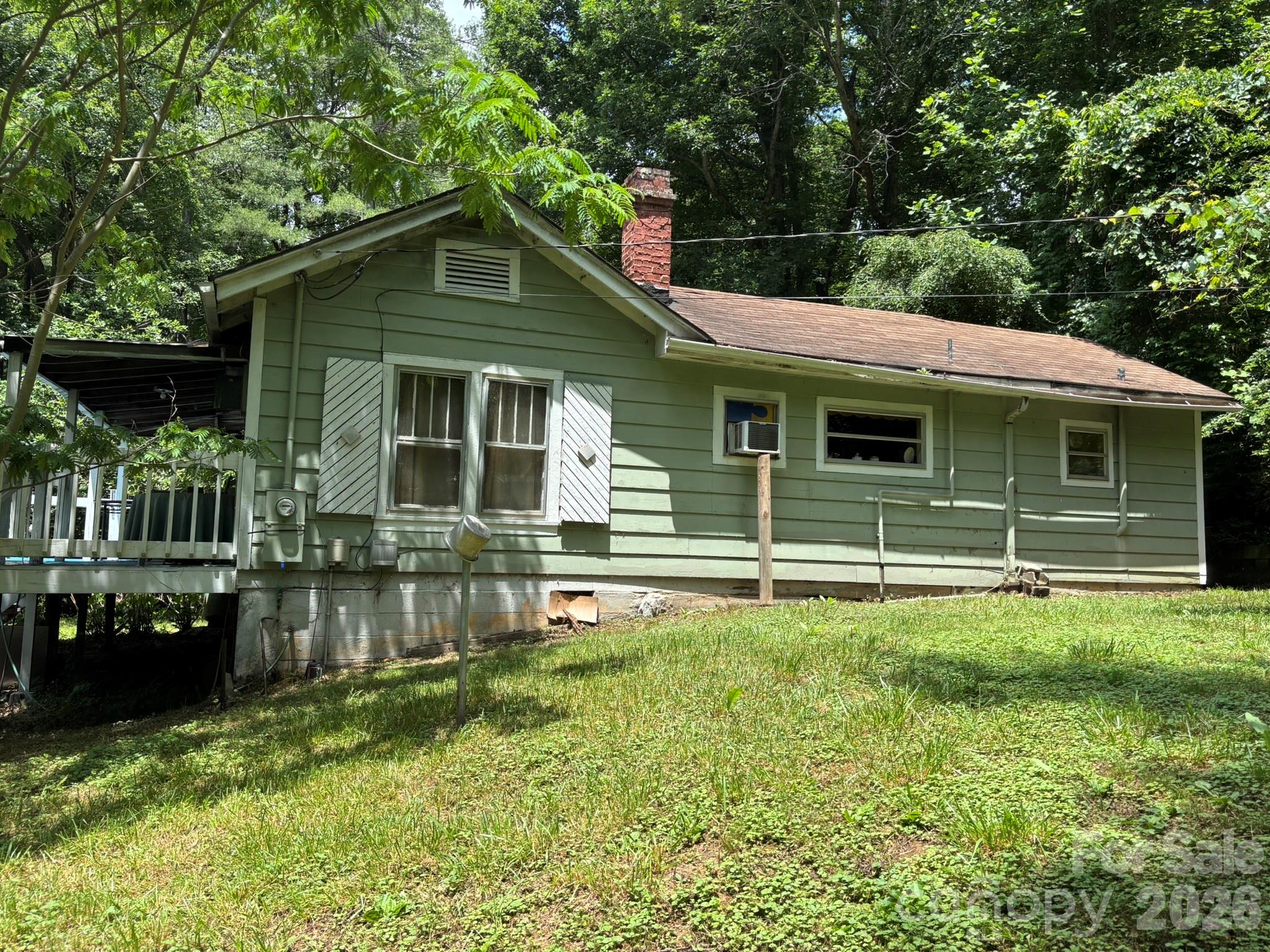 Find your own private oasis in the beautiful Avery's Creek area! This cute bungalow is all about the potential. The setting is gorgeous with a lush/level lot and creek running along the entire right side of the property (not in a flood plain/house is elevated/does not flood). In its better days this was the backdrop for campfires, summer fun in the water, and the stuff childhood dreams are made of. All it would take is a good weedeater and a machete to open this area back up. The house is set well off the road and it's very quiet. You can listen to the babbling creek from the covered porch and deck and enjoy gorgeous views of the mature yard. The interior needs an overhaul to reach its full potential. The office "could" serve as a 2nd bedroom but this is the access area to the bath. A remodeled version of this home would be ideal for owner occupants and investors alike, and it would honestly make a killer vacation rental! The location is ideal.... less than 10 minutes to I-26, and 10-15 minutes to AVL Airport, Blue Ridge Parkway, NC Arborteum, French Broad River, hiking, kayaking, and all kinds of restaurants, shopping, etc. on Long Shoals Rd. This one won't make sense for everyone, but the buyer that restores the beauty to this home will certainly reap the rewards in the long run! Sold "As Is, No Repairs". Seller will not make repairs.