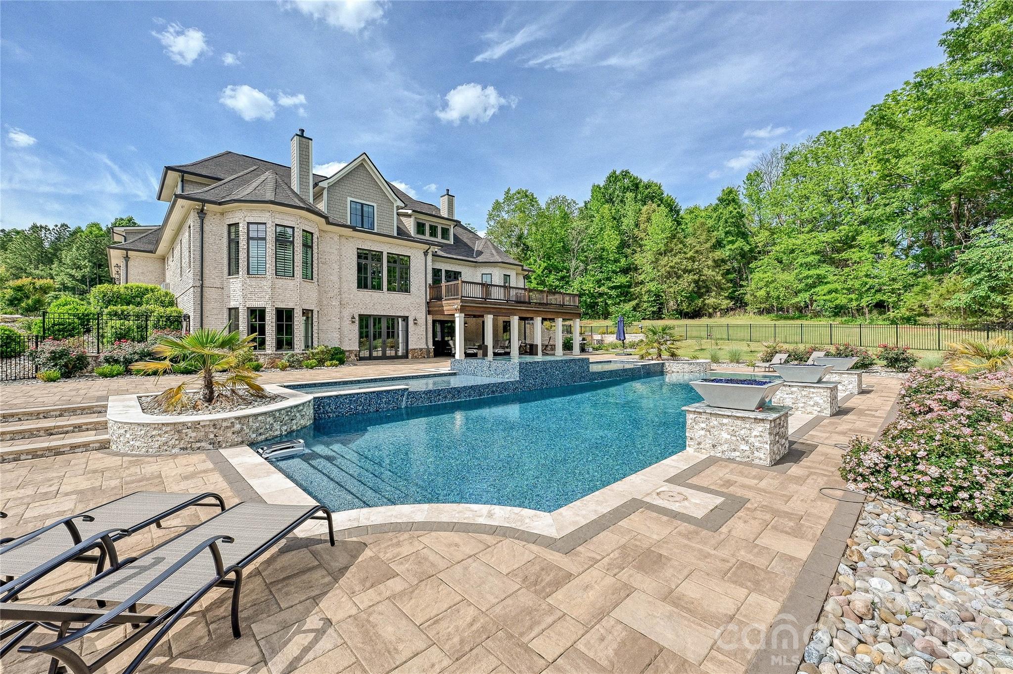 Extraordinary custom-built estate nestled on 20.84 private acres in the prestigious Oak Grove Farm community. Completed in 2023 and thoughtfully designed for both everyday living and entertaining, this exceptional property offers over 8,400 square feet of refined living space with a seamless blend of luxury, comfort, and functionality.

From the moment you arrive, the setting feels private and serene, with mature trees, beautiful natural surroundings, and endless opportunities to enjoy the outdoors. Inside, the home is filled with curated designer finishes, timeless craftsmanship, and inviting living spaces anchored by a stunning chef’s kitchen featuring premium appliances, custom cabinetry, and expansive gathering areas.

The fully finished lower level was designed for entertaining, complete with a second full kitchen, wine cellar, billiards area, recreation spaces, and direct access to the resort-style outdoor living areas. Enjoy a heated pool and spa, covered porches, outdoor fireplace, and spacious patios designed for year-round enjoyment.

The acreage offers the rare combination of privacy and flexibility, with room for trails, recreational use, additional structures, or simply enjoying the peaceful setting. Additional features include whole-house generators, extensive storage, a walk-in pantry, sauna, hot tub, and oversized garage space.

A truly special offering that combines luxury, land, and lifestyle in one of Waxhaw’s most desirable communities.