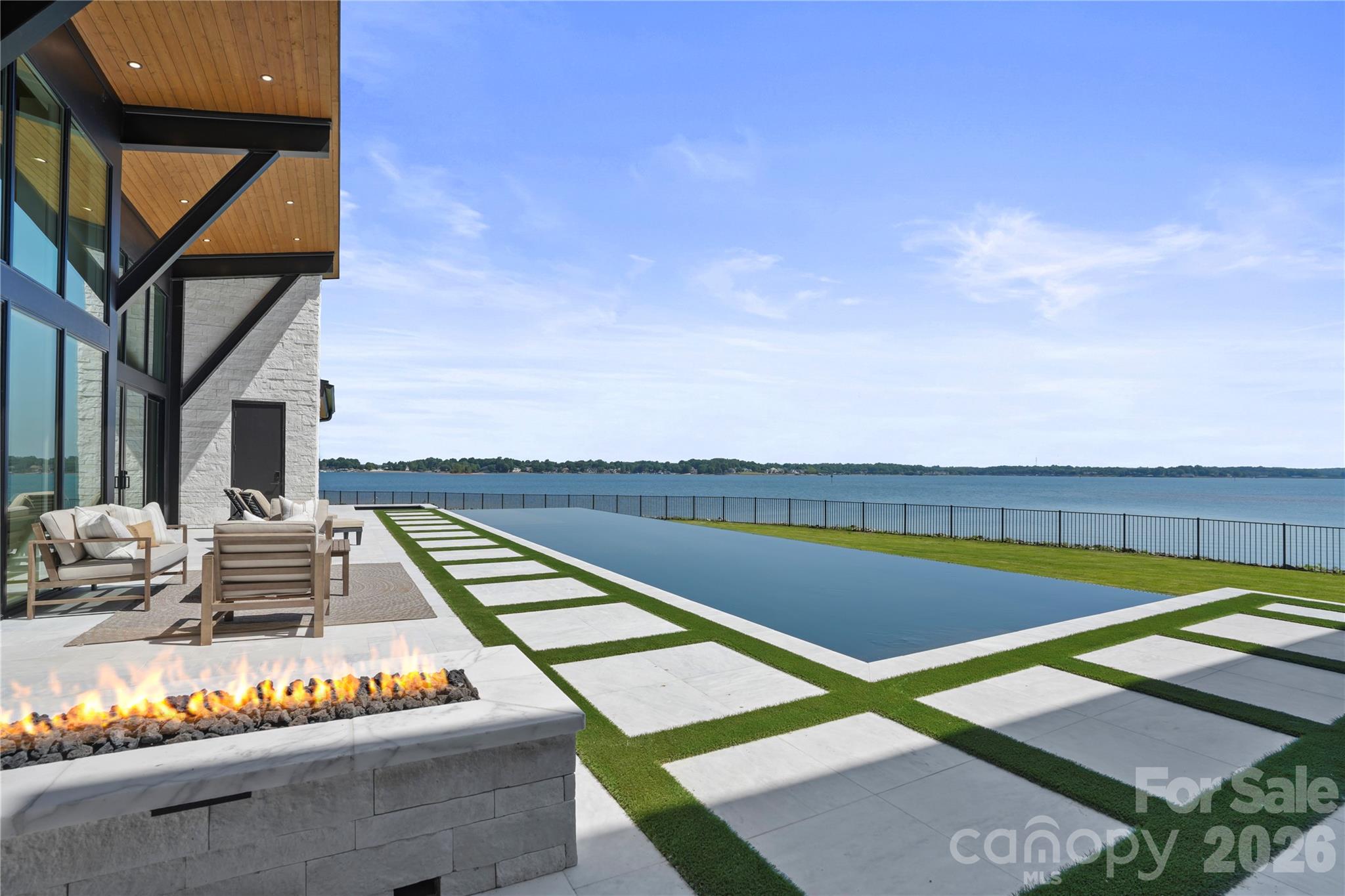 Perched on one of the most coveted peninsulas on Lake Norman, this extraordinary modern waterfront estate is a true architectural masterpiece designed to maximize every inch of its breathtaking homesite. Offering over 200 feet of shoreline, panoramic water views, and unmatched craftsmanship, this is a rare opportunity to own a one-of-one residence that simply cannot be replicated.

Thoughtfully designed by renowned home designer Tony Frazier and brought to life by Grand Living Homes, the home seamlessly blends modern architecture with its natural surroundings. Expansive walls of glass capture stunning lake views from nearly every room, including the great room, lakefront lounge, owner’s retreat, secondary bedrooms, fitness studio, and entertaining spaces throughout.

The attention to detail is remarkable. Dramatic steel beams transition from the interior to the exterior, while rich wood-tone soffits flow seamlessly from outside to inside, creating a level of architectural continuity rarely seen.

A striking entrance with 5' Pivot Door and mono-stringer staircase with cable railing serves as a centerpiece, complemented by custom finishes and craftsmanship at every turn.

The chef’s kitchen is designed for both everyday living and grand-scale entertaining, featuring premium Sub-Zero and Wolf appliances, wine refrigeration, beverage centers, ice makers, and custom cabinetry throughout.

The resort-style outdoor living experience rivals the finest luxury destinations. Enjoy a spectacular custom pool featuring a rare dual-sided infinity edge, integrated spa, outdoor kitchen, fire pit, expansive entertaining terraces, and endless views of Lake Norman. A newly completed covered dock with a 10,000-pound boat lift provides immediate access to lake life.

The owner’s retreat offers a private sanctuary overlooking the water, while additional amenities include a sauna, cold-plunge preparation, a flexible study/fitness room that can serve as a sixth bedroom, abundant storage, and a three-car garage with epoxy flooring and dedicated storage areas. Additional exterior storage accommodates wakeboards, skis, paddleboards, and other lakefront equipment.

Accessed through a private gated entrance, this estate delivers the ultimate combination of privacy, luxury, and convenience. 

Located just minutes from I-77, Catawba Avenue, and Torrence Chapel Road, you’ll enjoy one of Cornelius’ most desirable waterfront locations while remaining close to dining, shopping, and everyday conveniences.

Why wait years to design and build a custom waterfront estate of this caliber when this architectural showpiece is ready today?

This is more than a home, it’s a landmark property, a statement of design, and one of the most unique opportunities available on Lake Norman. 

Welcome to waterfront living without compromise.