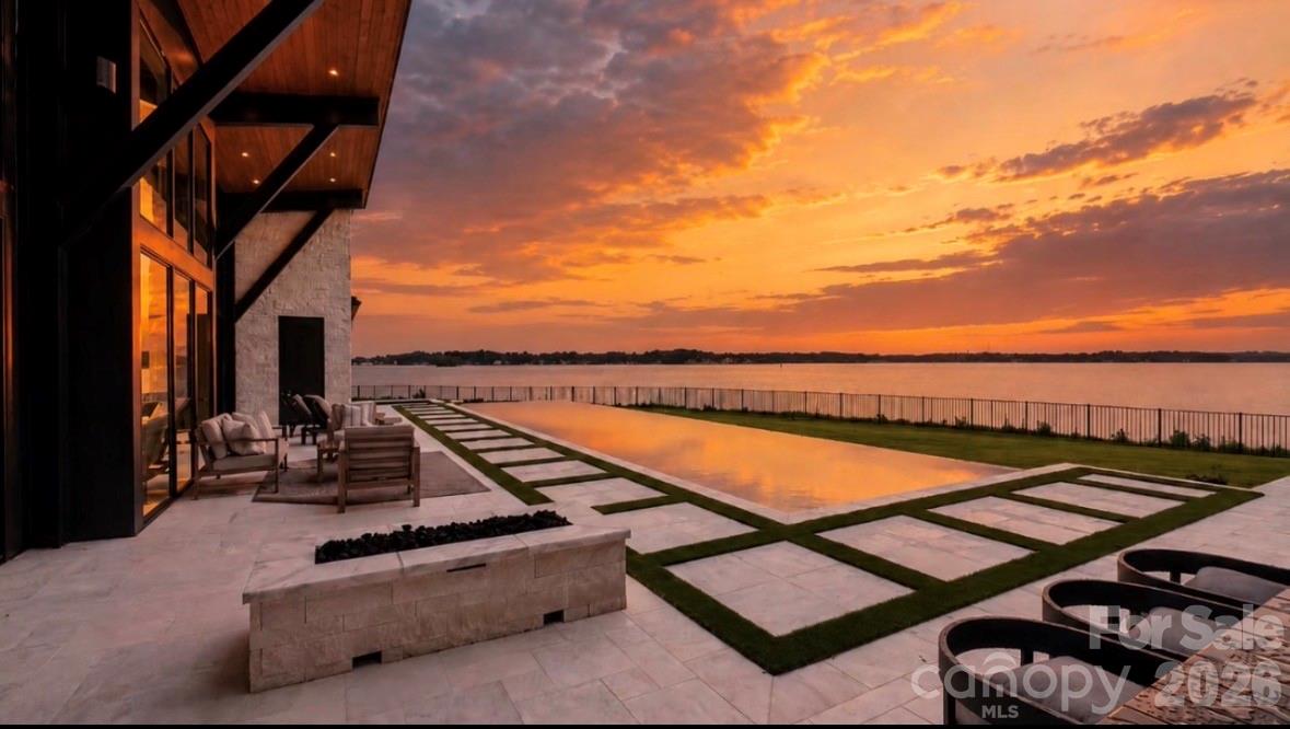 Perched on one of the most coveted peninsulas on Lake Norman, this extraordinary modern waterfront estate is a true architectural masterpiece designed to maximize every inch of its breathtaking homesite. Offering over 200 feet of shoreline, panoramic water views, and unmatched craftsmanship, this is a rare opportunity to own a one-of-one residence that simply cannot be replicated.

Thoughtfully designed by renowned home designer Tony Frazier and brought to life by Grand Living Homes, the home seamlessly blends modern architecture with its natural surroundings. Expansive walls of glass capture stunning lake views from nearly every room, including the great room, lakefront lounge, owner’s retreat, secondary bedrooms, fitness studio, and entertaining spaces throughout.

The attention to detail is remarkable. Dramatic steel beams transition from the interior to the exterior, while rich wood-tone soffits flow seamlessly from outside to inside, creating a level of architectural continuity rarely seen.

A striking entrance with 5' Pivot Door and mono-stringer staircase with cable railing serves as a centerpiece, complemented by custom finishes and craftsmanship at every turn.

The chef’s kitchen is designed for both everyday living and grand-scale entertaining, featuring premium Sub-Zero and Wolf appliances, wine refrigeration, beverage centers, ice makers, and custom cabinetry throughout.

The resort-style outdoor living experience rivals the finest luxury destinations. Enjoy a spectacular custom pool featuring a rare dual-sided infinity edge, integrated spa, outdoor kitchen, fire pit, expansive entertaining terraces, and endless views of Lake Norman. A newly completed covered dock with a 10,000-pound boat lift provides immediate access to lake life.

The owner’s retreat offers a private sanctuary overlooking the water, while additional amenities include a sauna, cold-plunge preparation, a flexible study/fitness room that can serve as a sixth bedroom, abundant storage, and a three-car garage with epoxy flooring and dedicated storage areas. Additional exterior storage accommodates wakeboards, skis, paddleboards, and other lakefront equipment.

Accessed through a private gated entrance, this estate delivers the ultimate combination of privacy, luxury, and convenience. 

Located just minutes from I-77, Catawba Avenue, and Torrence Chapel Road, you’ll enjoy one of Cornelius’ most desirable waterfront locations while remaining close to dining, shopping, and everyday conveniences.

Why wait years to design and build a custom waterfront estate of this caliber when this architectural showpiece is ready today?

This is more than a home, it’s a landmark property, a statement of design, and one of the most unique opportunities available on Lake Norman. 

Welcome to waterfront living without compromise.