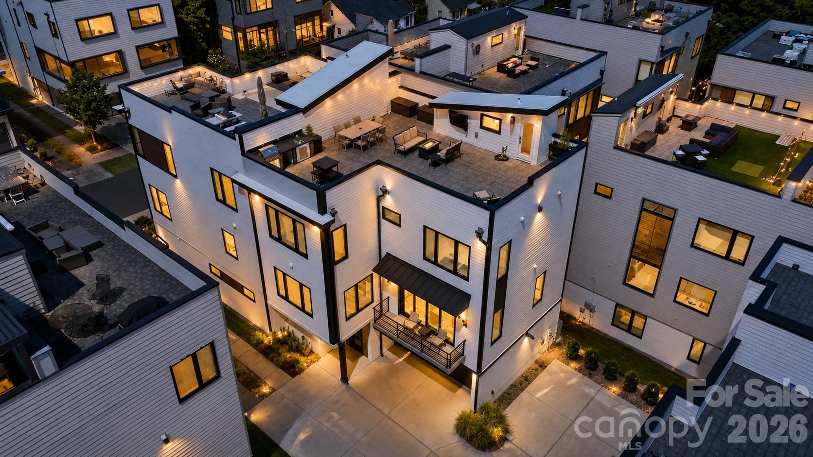 Experience elevated urban living in this exceptional contemporary residence in the highly sought-after Westbrook community, ideally positioned just moments from Uptown Charlotte, South End, Bank of America Stadium, Truist Field, Stewart Creek Greenway, Frazier Park, Camp North End, Charlotte Douglas International Airport, and an outstanding collection of restaurants, breweries, coffee shops, entertainment venues, shopping, and cultural attractions. Built in 2020, this thoughtfully designed four-bedroom, three-and-one-half-bath home offers more than 2,400 square feet of sophisticated living space that seamlessly blends modern architecture, designer finishes, functional living, and exceptional indoor-outdoor entertaining. The open-concept main level was thoughtfully designed to maximize natural light and flow, creating an inviting space equally suited for everyday living and entertaining. Wide-plank hardwood flooring extends throughout the main living areas, complemented by soaring ceilings, oversized windows, designer lighting, and a contemporary gas fireplace that anchors the spacious great room. The chef's kitchen serves as the centerpiece of the home, featuring custom cabinetry, an oversized quartz waterfall island with seating, stainless steel appliances, a gas range, abundant storage, a walk-in pantry, and a generous dining area. Sliding glass doors create a seamless transition to a covered balcony, extending the living space outdoors. The flexible lower level offers exceptional versatility and is currently configured as a private executive office. Complete with a full bathroom and wet bar, this space could also serve as a guest suite, media room, fitness studio, creative workspace, or secondary living area depending on individual needs. Its separation from the primary living spaces provides both privacy and functionality. The upper level serves as a private retreat highlighted by an expansive primary suite filled with natural light. The spa-inspired primary bathroom features dual vanities, a beautifully appointed oversized walk-in shower, contemporary finishes, and generous closet space. Two additional bedrooms, a full secondary bathroom, and a conveniently located laundry room complete the upper level, creating a practical and well-balanced floor plan. The true centerpiece of this residence is the spectacular private rooftop terrace, offering one of the most impressive outdoor living experiences in the area. Thoughtfully designed as an extension of the home's interior, this expansive rooftop retreat captures breathtaking panoramic views of the Uptown Charlotte skyline while providing multiple distinct entertaining spaces. Features include a built-in outdoor kitchen complete with grill, sink, and prep area, dedicated dining space, multiple lounge and conversation areas, mounted television, fire table, ambient string lighting, and incredible sunset views. Whether hosting family and friends, enjoying dinner under the city lights, or simply taking in Charlotte's skyline, this rooftop creates an unforgettable setting for year-round enjoyment. Additional highlights include an attached two-car garage equipped with EV charging capability, two additional dedicated exterior parking spaces adjacent to the residence, contemporary architectural design, energy-efficient newer construction, and a low-maintenance lifestyle with exceptional access to everything Charlotte has to offer. The location places residents within minutes of professional sporting events, concerts, greenways, parks, award-winning dining, nightlife, shopping, major employment centers, and all of the conveniences of Uptown Charlotte while offering the comfort and privacy of a boutique residential community. Combining sophisticated design, exceptional craftsmanship, thoughtfully designed living spaces, remarkable rooftop entertaining, and iconic skyline views, this residence presents a rare opportunity to own one of Westbrook's most distinctive contemporary homes.