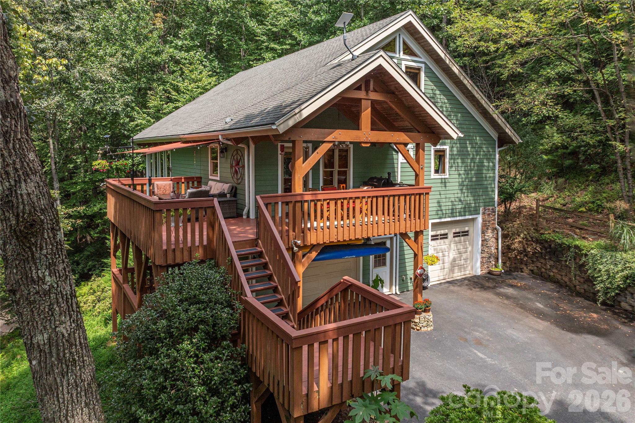 Tucked away in complete privacy just half a mile from High Vista's back entrance, this inviting mountain retreat offers quiet seclusion with everyday convenience. Surrounded by woods with seasonal winter views, the home is designed featuring a spacious wraparound deck ideal for gatherings or simply enjoying the peaceful forest setting. The home is configured with four bedrooms (served by a three-bedroom septic system), offering flexibility for guests, office space, or hobbies. The main floor features the primary suite, a second bedroom and full bath, along with the kitchen, dining space, and a family room with a soaring post and beam ceiling and stone, gas fireplace. Upstairs you’ll find another bedroom, a full bath, and a flexible loft, while the lower level includes a spacious guest suite along with the game room.  The standout game room is ready for fun from day one—complete with a home cinema projector and eight-foot screen, seating,  bar with a built-in beer tap and refrigerator, custom dart board, and an available brand new pool table. Whether hosting friends or enjoying a cozy night in, this space delivers.  As an added bonus, a membership to the High Vista Amenities Association is included with the house purchase, providing access to the pool, tennis and pickleball courts, a neighborhood pub, and a full calendar of community events. The home is less than ten minutes from everyday essentials, including a new Publix, an Ingles and four local breweries. Come home!