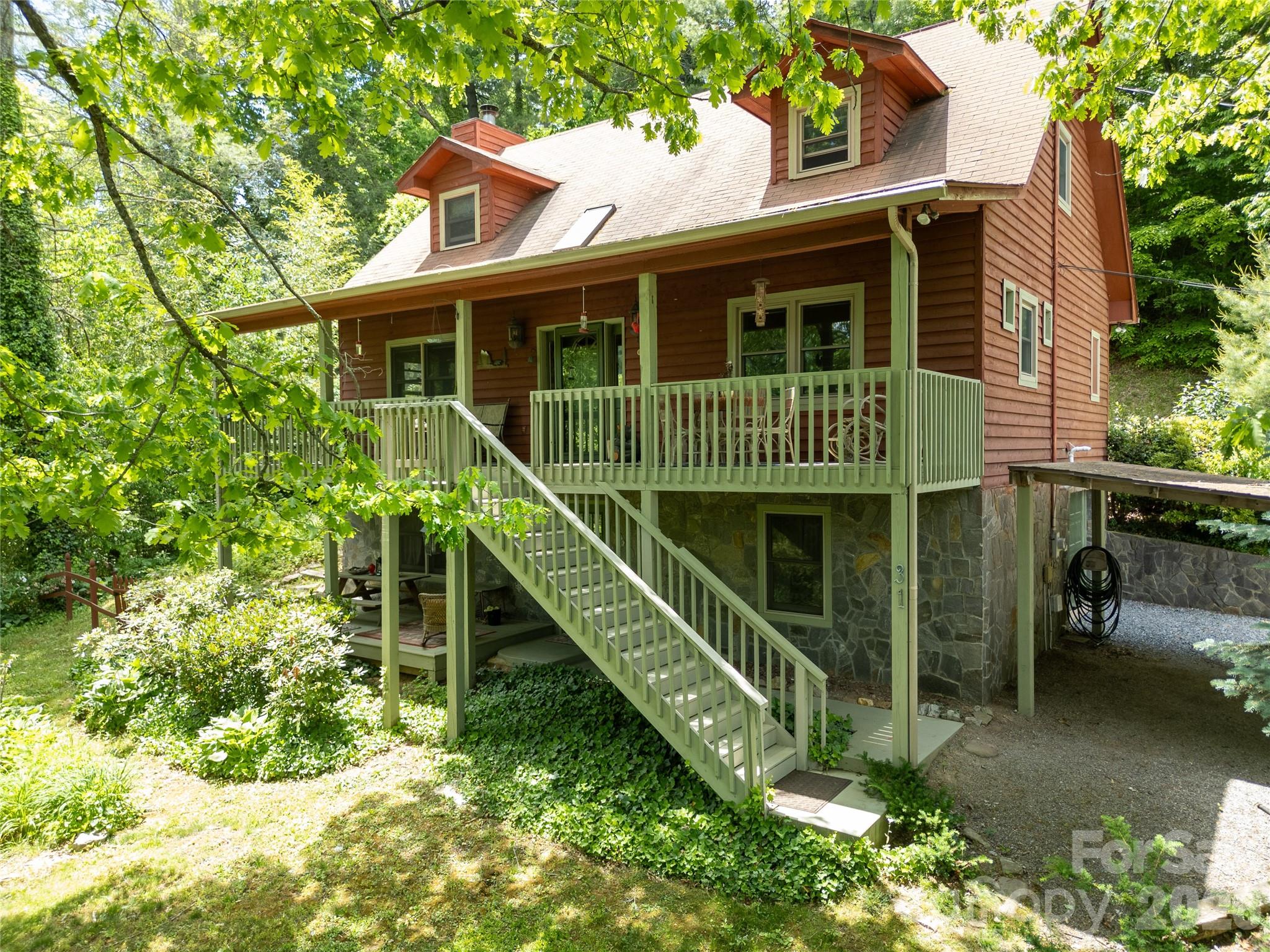 Tucked into the Cataloochee Heights area of Waynesville, 31 Valley Cove Place offers the ease of year-round mountain living with the character, warmth, and flexibility buyers hope to find in a true mountain home. The main residence features all main-level living with 2 bedrooms, 2 baths, wood and tile floors, a beautiful stone fireplace, leathered granite countertops, pantry storage, Miele appliances and striking wood posts that give the home an inviting, crafted feel. The upper level offers an open loft, bedroom and full bath creating flexibility for either level to serve beautifully as a primary suite.

Thoughtful updates include a new roof and HVAC in 2024. Layers of covered decks extend the living space outdoors, overlooking a gorgeous yard with mature plantings, raised garden beds, greenhouse and a creek along the property border. The separate 762-square-foot apartment includes a full kitchen and bath with its own exterior access—ideal for guests, extended family, work-from-home space or added flexibility for second-home use.

Driveway access is available on both levels, making daily living, unloading, and apartment access especially convenient. Located near Cataloochee Valley, with evening elk sightings in nearby fields, this property offers a wonderful blend of privacy, beauty, access, and mountain charm. Offered fully furnished with hard furnishings including many beautiful antiques. A rare offering where thoughtful updates, flexible living spaces, garden beauty, and the quiet magic of Cataloochee come together in one deeply inviting mountain property.