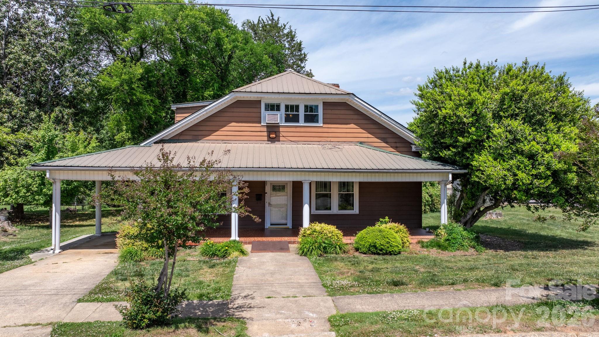 VERY MOTIVATED SELLERS! Another Huge PRICE REDUCTION, Over $50k below tax value! All new flooring in 4 ROOMS!  A rare opportunity to own one of Maiden's most charming and solidly-built Craftsman Bungalows.  With 4 BR and 2 full baths, this home is situated on Main Street in the heart of the "Biggest Little Football Town In the World," With a .38 acre lot, this gracious 1930s home offers nearly 2,900 square feet of generous, light-filled rooms — including spaces with soaring 10-foot ceilings and character that is simply aren't found in modern construction. You already have a metal roof, replacement windows, and updated wiring so 3 typical major renovation expenses have been met.  The home is move-in ready with great bones, and presents an exciting canvas for the buyer with vision. The oversized kitchen and dining area is brimming with potential — ready for the stunning renovation it deserves. Original hardwood floors grace multiple rooms, some new flooring is being put down as well. Warm knotty pine paneling adds character. Close to everything, you can walk to Church, an ice cream shop, or the local barber.  You won't find a nicer home for this price with this much square footage.  Only 43 mintues to Charlotte Douglas International Airport.
