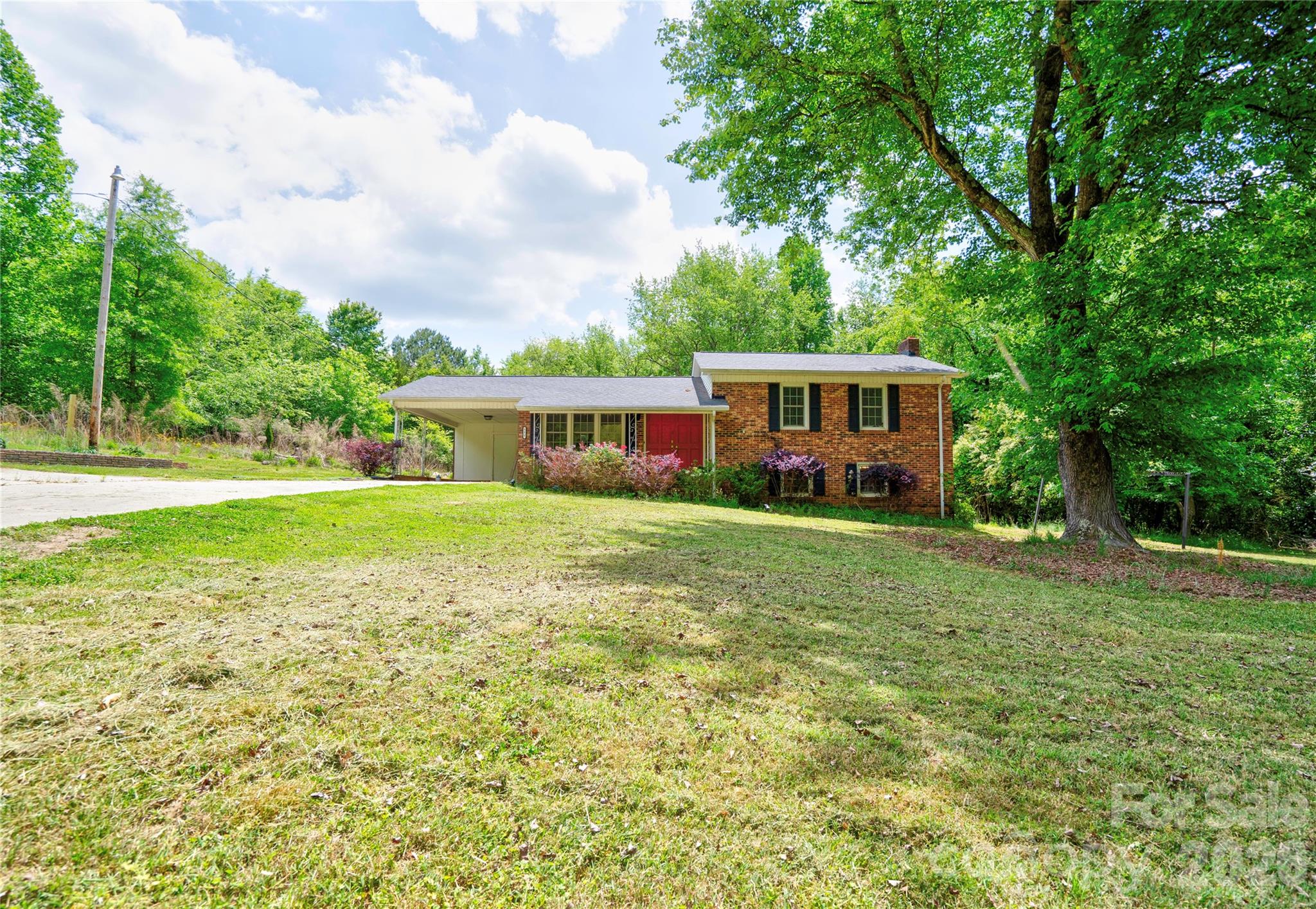 Spacious 3 Bedroom, 3 Bath brick split-level home offers room to spread out both inside and out! Situated on approximately 0.643 acres, this property features a large, partially shaded front and backyard—perfect for relaxing, entertaining, or play.  The main level includes a comfortable living room, dining area, and kitchen, creating a functional layout for everyday living. Upstairs, you’ll find three bedrooms and two full baths, including a private primary suite. The lower level adds even more versatility with a cozy family room featuring a classic brick fireplace, a full bath, laundry area, and a bonus room ideal for a home office, playroom, or additional living space.  Enjoy outdoor living from the covered front porch and take advantage of the single attached carport with storage room, extra parking pad, and an additional storage building for all your needs.  This home offers space, flexibility, and charm.  Don’t miss your opportunity to make it yours!