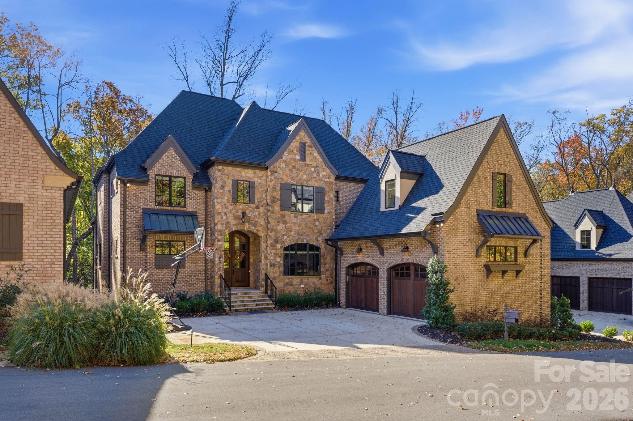 Stunning European-inspired custom home by Grandfather Homes, completed in 2023, located in the highly sought-after Chambery neighborhood. This exceptional 2 story residence with full basement offers 6,956 sq ft of thoughtfully designed living space on a 0.32-acre lot with 6 bedrooms, 5 full baths, and 2 half baths.
The open-concept main level features soaring ceilings, refined architectural details, hardwood floors, and designer finishes throughout. The chef’s kitchen is equipped with quartz countertops, a large island, double ovens, and an expansive walk-in pantry with built-in refrigerator/freezer, coffee bar, and adjoining scullery with second sink, dishwasher, and additional storage.
The main-level primary suite offers a spa-like bath and spacious walk-in closet. Additional highlights include two laundry rooms (main and upper), a mudroom, and custom closets throughout.
Upstairs features generously sized bedrooms and well-appointed baths. The fully finished walk-out basement includes a private guest suite with en suite bath, fitness room, flex/media space, abundant storage, and a spacious living area with gas fireplace. Luxury vinyl plank flooring enhances durability in the lower level.
Enjoy outdoor living on the covered deck with fireplace overlooking a fenced backyard with mature landscaping. Additional features include brick and stone exterior, side-load 2-car garage, and multiple fireplaces. Ideally located near Charlotte’s premier shopping, dining, and amenities.