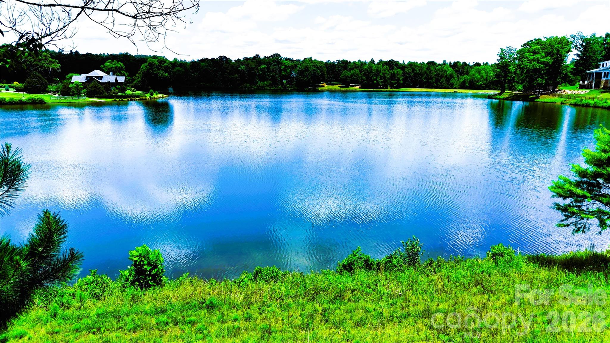 WELCOME TO ONE OF DERBYSHIRE'S PREMIER WATERFRONT HOMESITES ~
Featuring: The Lake Estate at Derbyshire - A Signature Waterfront Estate Opportunity in Horse Country!
Some places are built - Others are discovered - This is one of the rare few where your vision becomes part of the landscape! Perfectly positioned along the shores of beautiful Lake Sandy Plains within Derbyshire—one of Tryon/Columbus Horse Country's most distinguished gated, equestrian-oriented communities—this remarkable waterfront homesite presents an extraordinary opportunity to create a custom luxury residence where timeless architecture, breathtaking scenery, and an exceptional lifestyle come together in perfect harmony!
Whether you're envisioning a full-time residence, an elegant mountain retreat, or a legacy property to be enjoyed for generations, premier waterfront homesites within Derbyshire have become increasingly limited!!! With its peaceful setting, exceptional privacy, and captivating lake views, this property offers an opportunity that is becoming more difficult to find in today's luxury market - if not one of the last ones available! See for yourself!

Beyond the shoreline lies an exceptional canvas for your dream home! Expansive lake views framing an unforgettable backdrop! The gently sloping topography is ideally suited for an elegant walkout design, sophisticated main-level living, or a thoughtfully designed custom retreat that seamlessly blends indoor luxury with extraordinary outdoor living! 
Imagine beginning each morning with coffee overlooking the peaceful waters as the mist rises across the lake. Spend your afternoons kayaking, paddleboarding, canoeing, fishing, or simply enjoying the quiet beauty from your own shoreline. As evening settles in, gather with family and friends beside your resort-style pool, spa, or lakeside fire feature while the Carolina sky reflects across the water. Here, every season offers a new perspective, and every day feels like a retreat! See why many come to call it Home!
This Lake Estate offers buyers the flexibility to bring their own builder and architectural vision—or explore professionally designed luxury home concepts thoughtfully created for this homesite with/by the owner/builder. Depending on the selected package, buyers may have the opportunity to personalize floor plans, architectural elevations, luxury finishes, chef-inspired kitchens, expansive covered terraces, walkout lower levels, resort-style pools and spas, outdoor entertaining areas, and countless custom details designed to complement both the homesite and their lifestyle!
Life within Derbyshire extends far beyond the homesite itself. Centered around a private spring-fed lake, this exceptional community offers a peaceful blend of refined country living, equestrian heritage with beautifully maintained common areas, scenic walking opportunities, riding amenities, and convenient member access to the renowned CETA/FETA trail systems(*Verify per property). 
Minutes away, the internationally recognized Tryon International Equestrian Center offers world-class horse shows, training, dining, shopping, entertainment, and year-round events, making this an exceptional destination for equestrian enthusiasts + those seeking an elevated mountain-lake lifestyle!
For those searching for more than a site—for those seeking a place where luxury, nature, and lasting memories come together—This Lake Estate at Derbyshire offers an extraordinary opportunity to build not only the home you've imagined, but the lifestyle you've been waiting to live! 
Conveniently located near Tryon, Columbus, Landrum, I-26, Greenville-Spartanburg Intl Airport, Asheville Regional Airport, and Charlotte Douglas Intl Airport, you'll enjoy the perfect balance of peaceful privacy + everyday convenience!
**Separate MLS listing is also available for the lot only, allowing buyers the flexibility to secure this exceptional waterfront homesite today; build whenever the time is right.**