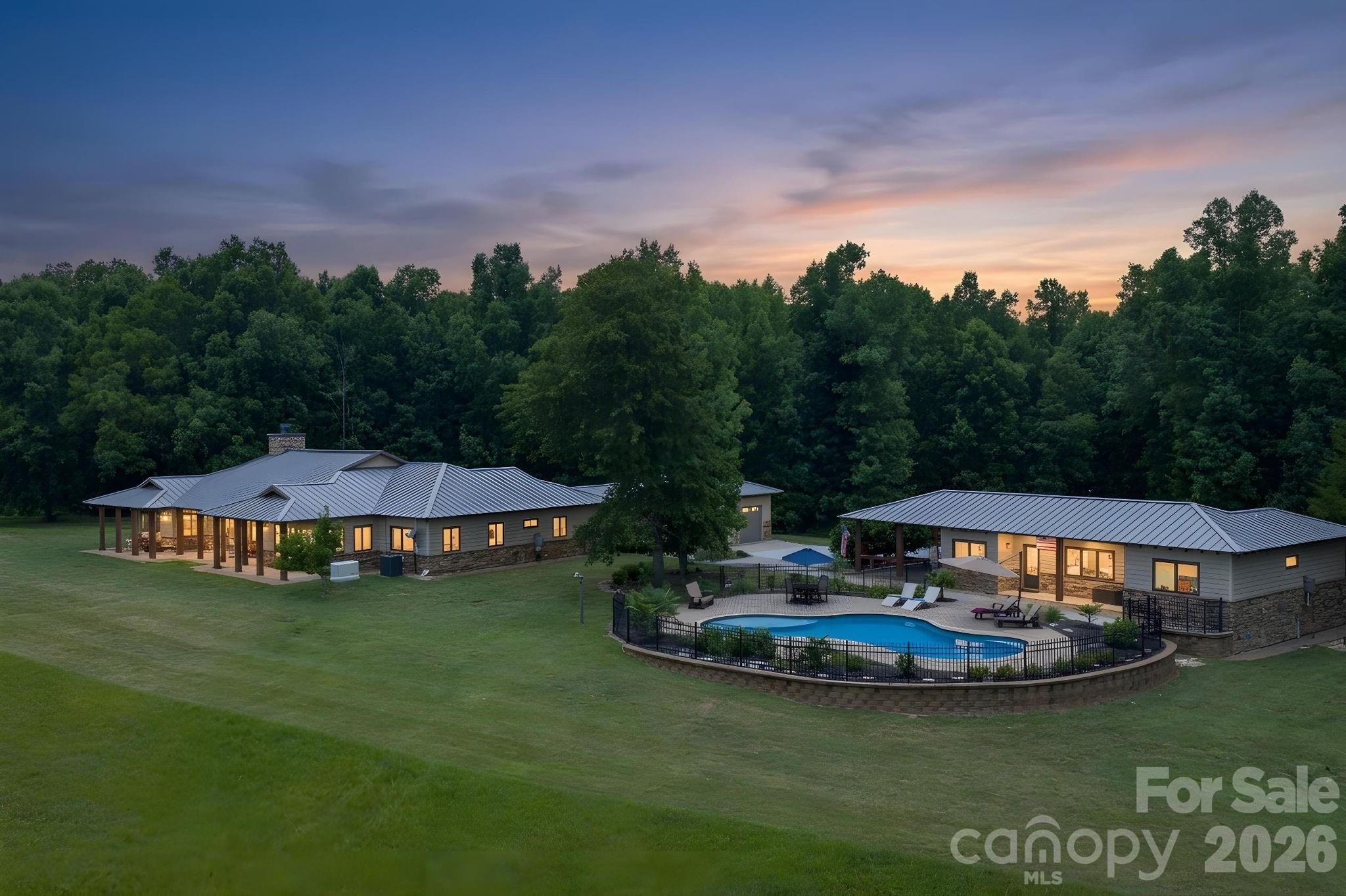 Whether envisioned as an equestrian estate, multigenerational retreat, sporting property or income-producing farm, this is the kind of place where generations can gather, spread out and make lasting memories.

Hidden behind an automatic gate and tucked away on more than 63 private acres, this remarkable estate offers a rare combination of privacy, recreation, equestrian amenities and income-producing potential, conveniently located between Waxhaw, Monroe, Lancaster and Wesley Chapel.

Long before reaching the home, the outside world begins to disappear. Trails wind through the woods, pastures stretch toward the horizon and a stocked pond provide the backdrop for a lifestyle that feels increasingly rare. Whether your passions include horses, fishing, hunting, riding ATVs or simply enjoying the outdoors, this property was designed to accommodate them all.

The custom one-level residence offers nearly 3,300 square feet with a split-bedroom design and wheelchair accessibility. At the center of the home, the kitchen, dining area and great room flow together beneath vaulted tongue-and-groove ceilings accented by exposed wood beams, skylights and a floor-to-ceiling stone fireplace. Granite countertops, custom cabinetry, Bosch appliances, gas range and an oversized island create spaces equally suited for everyday living and entertaining. Multiple glass doors connect the interior to covered patios, pergola and built-in gas grill overlooking the surrounding landscape.

The primary suite features a custom closet completed in 2025, spacious bath with wheel-in shower and garden tub, while the guest suite includes a private bath and adjoining flex room ideal for an office or sitting room.

Outdoor living is every bit as impressive as the interior. The gunite saltwater pool was resurfaced with PebbleTec in 2024 and is complemented by paver patios, outdoor shower and fire pit gathering area. The approximately 2.85-acre stocked pond offers bass, catfish, crappie and bream fishing, while trails throughout the acreage invite horseback riding, hiking and ATV adventures.

The separate 1,000-square-foot pool and guest house includes a kitchen, recreation room, two flex rooms, full bath and covered porch, providing ideal accommodations for guests, extended stays or income-producing opportunities. An apartment above the barn offers additional flexibility.  

Equestrians will appreciate the exceptional facilities including an eight-stall barn with automatic waterers, wash stall, tack room, feed room and hay loft. A covered 100' x 200' arena, large turf Grand Prix field, board-fenced pastures, trailer parking and riding trails create a setting equally suited for pleasure riding, training or boarding.

Outdoor enthusiasts will appreciate the abundant wildlife, wooded acreage and private shooting range. Hunting, ATV trails and excellent fishing create a year-round playground, while hay production and existing infrastructure provide additional income opportunities.

Multiple support buildings include a workshop and four-bay steel building for tractors, trailers and recreational vehicles. Recent improvements include the automatic gate, pool resurfacing, HVAC systems, water filtration, well upgrades and a Generac generator installed in 2026.

Properties combining this level of privacy, recreation and functionality are becoming increasingly difficult to find. More than simply a horse farm, this is the kind of place where holidays become traditions, memories are made and everyone eventually finds their way back home. Because some places are more than where you live.

Septic system is an engineered drip system, available documentation shows system for 2 bedroom home and 2 bedroom guest house, yet the guest/flex rooms in the guest house do not have closets.