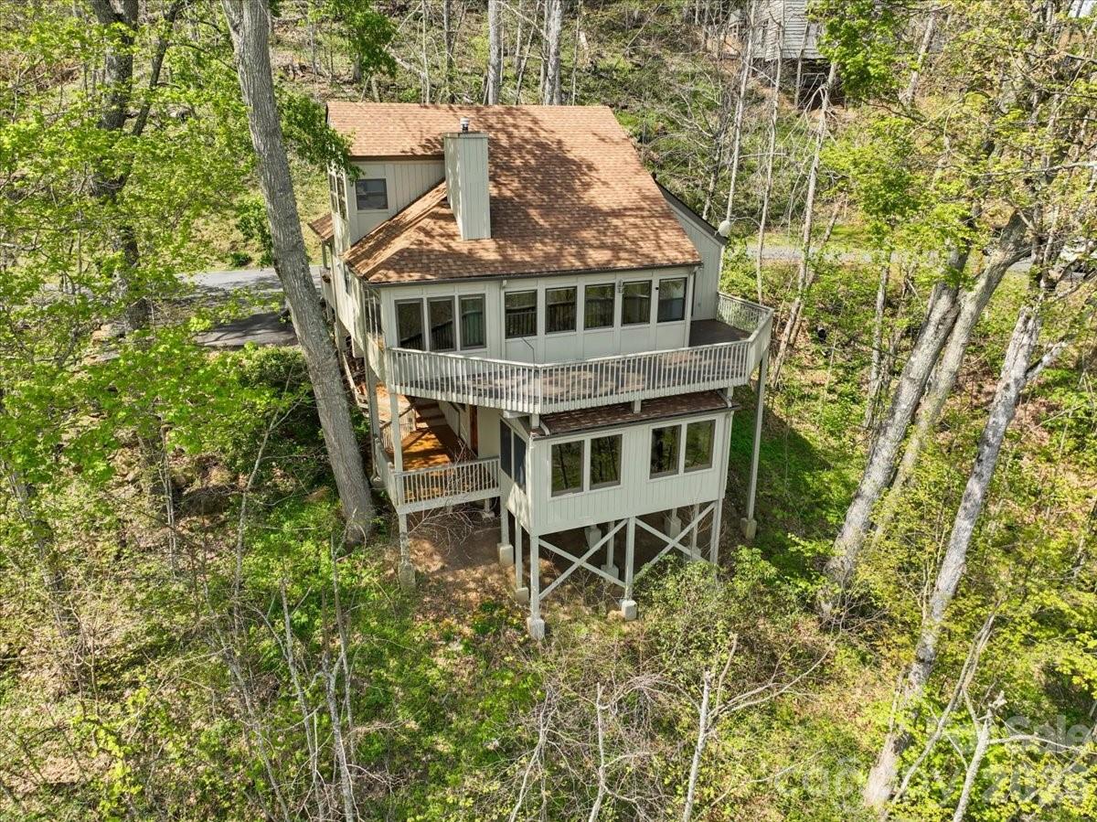 Set on a uniquely positioned homesite with breathtaking long-range mountain views, this beautifully updated and expanded 4-bedroom, 4-bath home in MOUNTAIN AIR offers a rare combination of privacy and connection to the surrounding landscape. With no homes directly above, below, or on one side, the property enjoys a level of seclusion generally reserved for the mountain’s custom home neighborhoods. The home’s square footage exceeds most other Neighborhood Homes, creating generous living space rarely found in this setting. It has been thoughtfully enhanced with the addition of a welcoming covered front porch, a dining room, and a pool room/library, along with a side deck perfectly positioned to capture the cool mountain breezes of summer. The fully remodeled kitchen serves as the heart of the home, featuring custom alder cabinetry, remarkable marble countertops whose flowing greens and warm browns echo the branches and forest beyond, and GE Profile appliances approximately 1.5 years old. A water feature crafted from the same marble as the countertops enhances the natural flow of the space, cultivating a tranquil and welcoming atmosphere. Heritage maple engineered hardwood flooring runs throughout the main living areas, complemented by custom blinds and nature-inspired Tiffany lighting.
Distinctive artisan details include a custom mountain laurel stair railing, a handcrafted maple mantelpiece selected specifically for the space and carefully cured and crafted over the course of a year, new alder interior and exterior doors, and custom built-ins in both the bedroom and den. Upstairs, recent updates include new carpet, a new mini-split system, and a completely remodeled bathroom. 
The property has also benefited from recent tree trimming to further open and highlight the expansive long-range views, enhancing both the setting and natural light.  Additional practical features include under-house golf cart storage, a fenced dog-potty yard, and built-in overhead exterior storage that blends seamlessly with the home’s structure, adding convenience to everyday mountain living.  With its coveted top-of-the-mountain location, thoughtful renovations, generous living space, and unforgettable mountain views, this home offers a truly inviting mountain lifestyle in one of the community’s most desirable settings. MOUNTAIN AIR property owners enjoy all paved access, 24/7 manned guard-gate, multiple parks, hiking trails, and a private runway! Optional club memberships available. Ideal as a full-time residence, vacation getaway, or short-term rental investment. Located just minutes to the town of Burnsville and a short drive to Asheville, NC and Johnson City, TN.