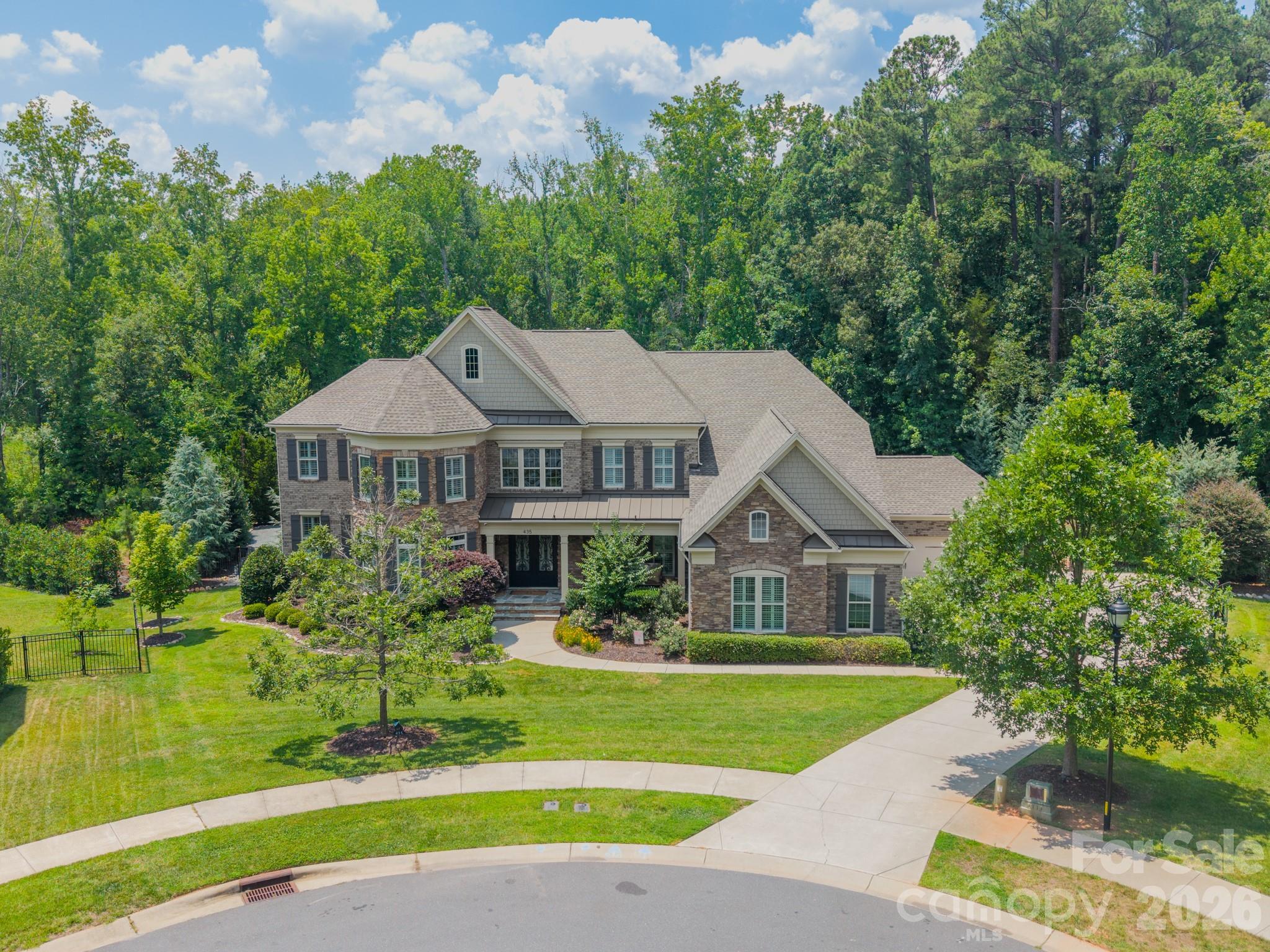 Designed for those who appreciate exceptional craftsmanship, effortless entertaining, and resort-style living, this stunning custom home in The Falls at Weddington offers over 6,000 square feet of thoughtfully designed living space where every detail has been carefully considered.

Beyond the front door, a dramatic oak double staircase sets the tone for the elegant interior. Coffered ceilings, spacious gathering areas, a dedicated media room, and designer finishes create a warm yet sophisticated atmosphere. The chef's kitchen is beautifully appointed with premium appliances, custom cabinetry, generous workspace, and seamless flow into the main living areas, making it ideal for both everyday living and entertaining. Spacious secondary bedrooms each feature walk-in closets and are complemented by a versatile loft, while the luxurious primary suite offers a custom-designed walk-in closet and a beautifully appointed spa-inspired bath.

The backyard is the true showpiece of this exceptional property. Designed as a private retreat, the outdoor living space offers remarkable privacy, mature landscaping, and an atmosphere of serenity rarely found. The heated and chilled saltwater pool and spa are surrounded by elegant travertine hardscaping and beautifully designed gathering spaces that invite relaxation throughout the year. An expansive pavilion serves as the heart of the backyard, featuring a floor-to-ceiling stone fireplace, motorized screens for year-round comfort, and a fully equipped outdoor kitchen complete with an imported Italian pizza oven. An outdoor bath, tranquil koi pond, gas lanterns, professional landscape lighting, and thoughtfully designed entertaining areas complete this extraordinary outdoor experience.

Located within one of Weddington's most desirable communities, residents enjoy exceptional amenities including a clubhouse, community pool, playground and walking trails. Top-rated Weddington schools, shopping, dining, and major commuter routes are all just minutes away.

This is more than a beautiful home—it's a place designed for gathering, entertaining, and creating lasting memories while enjoying the very best of luxury indoor and outdoor living.