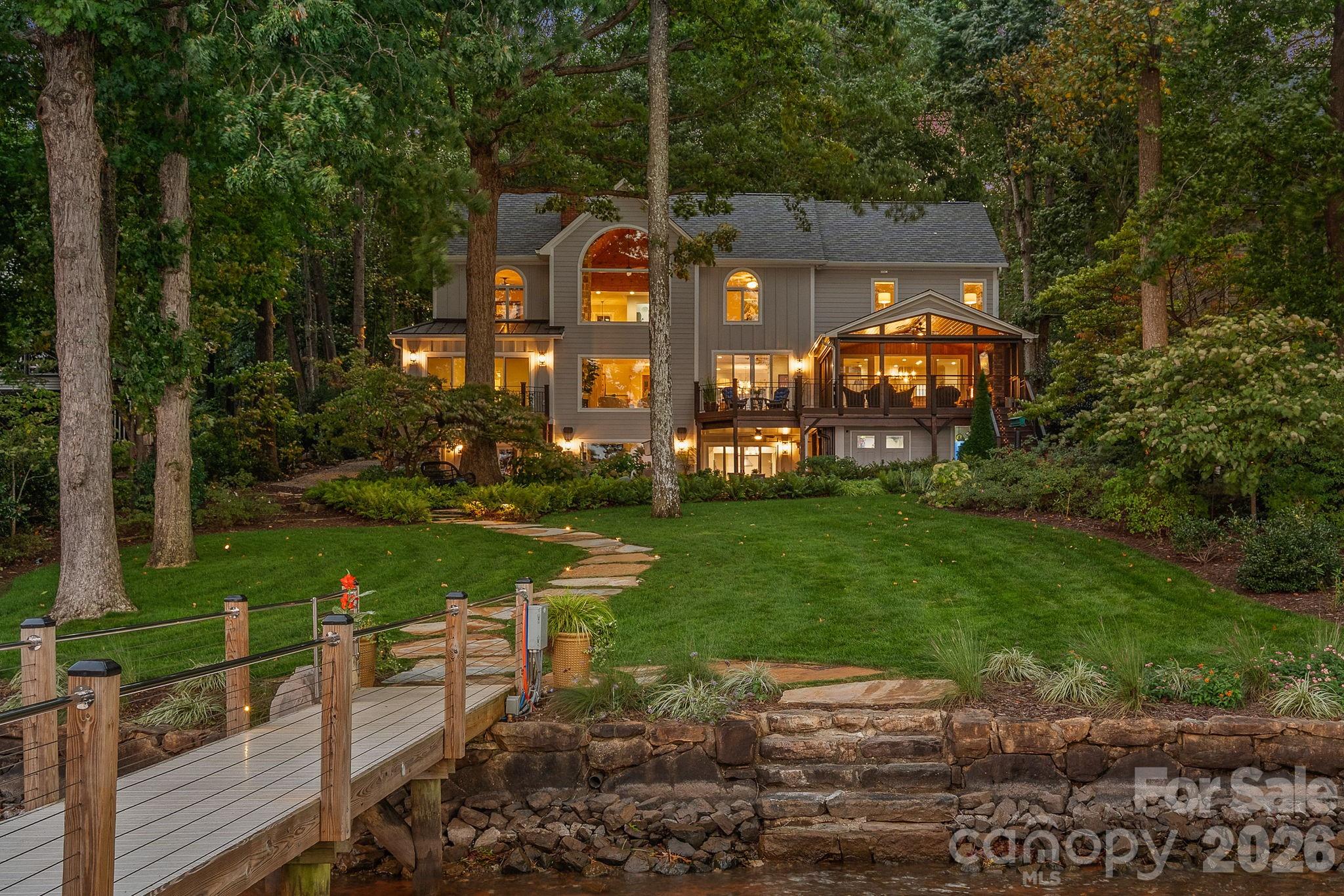 A one-of-a-kind waterfront estate on Lake Norman, fully transformed through a renovation completed in 2025 and ideally located just outside Cornelius in one of the lake’s best-kept secret neighborhoods. Blending timeless Southern charm with modern luxury, this exceptional property is perfectly positioned on a one-acre, tree-filled lot with resort-style amenities and breathtaking long-range water views.. Walls of glass and expansive sliding doors frame sweeping big water views and breathtaking sunrises, while rare deep water at the double-slip dock allows for swimming and diving right from your backyard.

The thoughtfully designed interior balances warmth and sophistication, anchored by a soaring two-story natural stone fireplace, wide-plank Caribbean floors, and designer finishes throughout. A first-floor primary suite offers a private balcony with panoramic views, spa-inspired bath with heated marble floors, custom shower, and a spacious walk-in closet/changing room. The chef’s kitchen features an expansive island, Sub-Zero refrigerator, scullery with custom pantry, and adjacent lounge with wine fridge. 

Designed for the gracious indoor-outdoor living that defines the Carolina lifestyle, the lake-level retreat includes a second kitchen, bourbon room, game room, and direct walk-out to a flagstone terrace with stone fireplace. Enjoy year-round living from the serene screened porch with hurricane shutters, or stroll past the koi pond and waterfall stream to your private dock with covered entertaining area, a high-powered boat lift, floating dock, and jet ski dock.

The grounds are truly a rare offering on Lake Norman - professionally designed with both beauty and livability in mind. Lush, layered landscaping blends mature trees, manicured lawns, and thoughtfully placed stonework to create both beauty and privacy. Expansive, usable yard space is a rarity on the lake, offering room to entertain, relax, or simply take in the water views from multiple vantage points. From the winding paths and tranquil water features to the seamless connection between indoor and outdoor living, every element of the landscape was intentionally designed to elevate the experience of lakefront living.

Every detail has been updated - hardboard siding, new roof, windows, HVAC systems, exterior stonework, custom lighting, irrigation, and professionally designed landscaping. The neighborhood enhances the lifestyle with a private beach, boat launch, pool, tennis/pickleball court and basketball court. Ideally located just minutes to shops, dining, and top schools, and less than 20 minutes to Uptown Charlotte and Charlotte Douglas International Airport, this estate offers an unrivaled blend of luxury, privacy, and convenience.  This is more than a home - it’s a lifestyle.