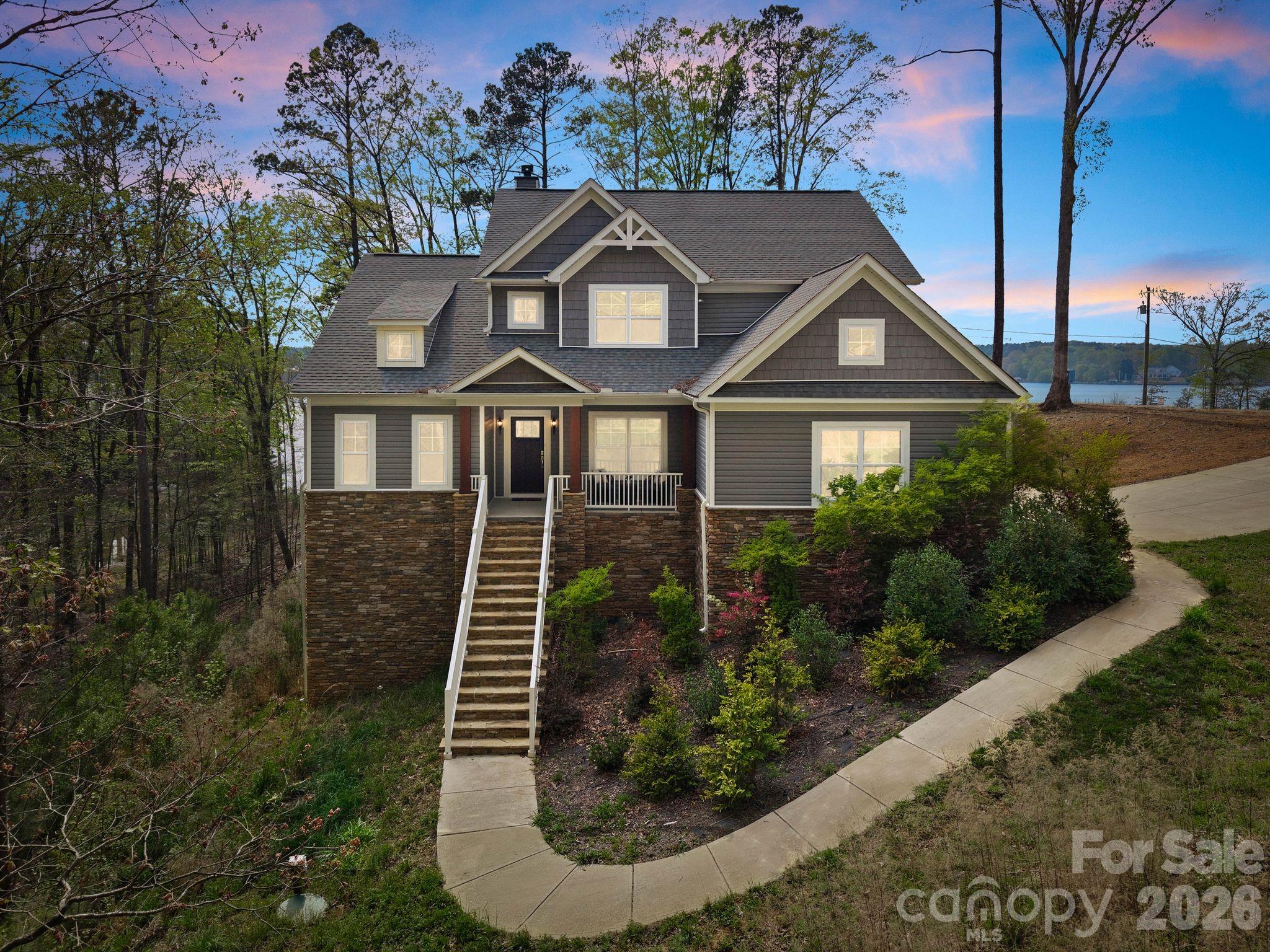 Sun-drenched interiors, soaring ceilings, and tranquil lake views define this refined Lake Wylie retreat on 3+ sprawling acres. Thoughtfully designed for both grand entertaining and effortless everyday living, the residence combines warm natural finishes with a crisp, modern palette to create an inviting, move-in–ready sanctuary on the lake.

A dramatic two-story great room anchors the main level, showcasing a floor-to-ceiling stone fireplace, rich wood-tone flooring, and an expansive wall of picture windows that frames the treetops and shimmering lake views beyond.  Designer lighting and carefully curated fixtures lend character, while the soft, neutral palette lets your furnishings and art take center stage. The open layout transitions seamlessly into a chef’s kitchen featuring a large island, granite countertops, farmhouse sink, stainless appliances, abundant cabinetry, a light-filled breakfast area overlooking the lake, and an oversized pantry. Generous dining and living areas offer a sophisticated backdrop for holidays, game days, and intimate gatherings alike flowing outdoors to the large wooden deck.

The main-level primary suite evokes a private spa, with a generous bedroom wrapped in windows, direct lake views, and a luxurious bath with dual vanities, freestanding soaking tub, and an impressive glass-enclosed shower. The primary closet offers exceptional storage and organization. A dedicated home office with barn doors creates a chic, quiet workspace bathed in natural light. A separate mud room and laundry room plus a stylish half bathroom for guests keep the main level beautifully organized and clutter-free.

Upstairs an airy loft/playroom provides yet another relaxing gathering space, with open sightlines to the great room below and captivating lake views. Two spacious bedrooms share a well-appointed Jack-and-Jill bathroom and enjoy generous closets.

The lower basement level extends the home’s livability with a large second family room and an additional bedroom perfect for a theatre, fitness studio, or private guest suite. The unfinished portion offers excellent storage and future potential, already plumbed for an additional bathroom or second kitchen.

With walls of glass capturing lake and wooded views from nearly every main living area, this residence embodies the effortless, indoor-outdoor Lake Wylie luxury lifestyle—simply bring your guests and a desire for retreat.

Enjoy nearby McDowell Nature Preserve, offering miles of scenic hiking trails, with convenient access to Shopton Road, Highway 160, and 49/South Tryon, as well as grocery, shopping, and dining at Rivergate. Marinas in the area provide both dry storage and wet slips, with Terry’s Marina and Love Cove Marina and Resort just a short golf cart ride or drive away. Newly paved road with no HOA.