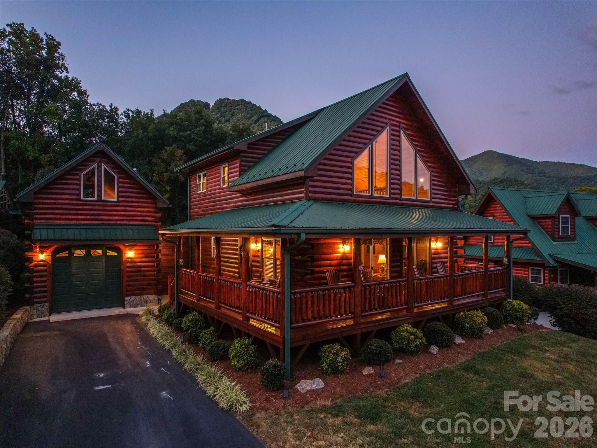 Discover this premier mountain cabin retreat blending timeless rustic charm with modern luxury. This home is being sold turnkey and fully-furnished. Nestled in a well-established cabin community on a level lot with year-round paved access, this home sits within walking distance to the vibrant heart of Maggie Valley. It offers effortless proximity to Cataloochee Ski Area, downtown Waynesville, the Asheville region, and Harrah’s Cherokee Casino. Step inside to an inviting open floor plan showcasing beautiful wood floors and soaring vaulted cathedral ceilings that create an atmosphere of spacious elegance. A dramatic floor-to-ceiling fireplace serves as the centerpiece of the living area, perfect for cozy gatherings after a day on the slopes or exploring the Smokies. The spacious gourmet kitchen impresses with granite countertops, a large island with breakfast bar, and abundant cabinetry—ideal for entertaining family and friends. The main-level primary suite provides convenience and privacy, featuring a luxurious ensuite bath with dual vanity, ceramic tile, and a spacious walk-in shower. Upstairs, an open loft area with a dramatic wall of windows frames breathtaking long-range mountain views, offering a serene spot for relaxation or a home office. Two additional bedrooms with vaulted ceilings and a full bath complete the upper level, providing ample space for guests.Outside, the custom log construction is complemented by a generous wraparound covered deck, perfect for al fresco dining while soaking in panoramic mountain vistas that captivate year-round. A detached single-car garage includes optional storage or bonus space above. The metal roof ensures durability and low maintenance, while the established community and proven short-term rental history deliver strong income-producing potential for investors or those seeking a turnkey vacation property. This rare offering combines authentic mountain living in one of Western North Carolina’s most desirable locations. Whether as a primary residence, second home, or lucrative rental investment, this log cabin delivers unparalleled lifestyle and value.