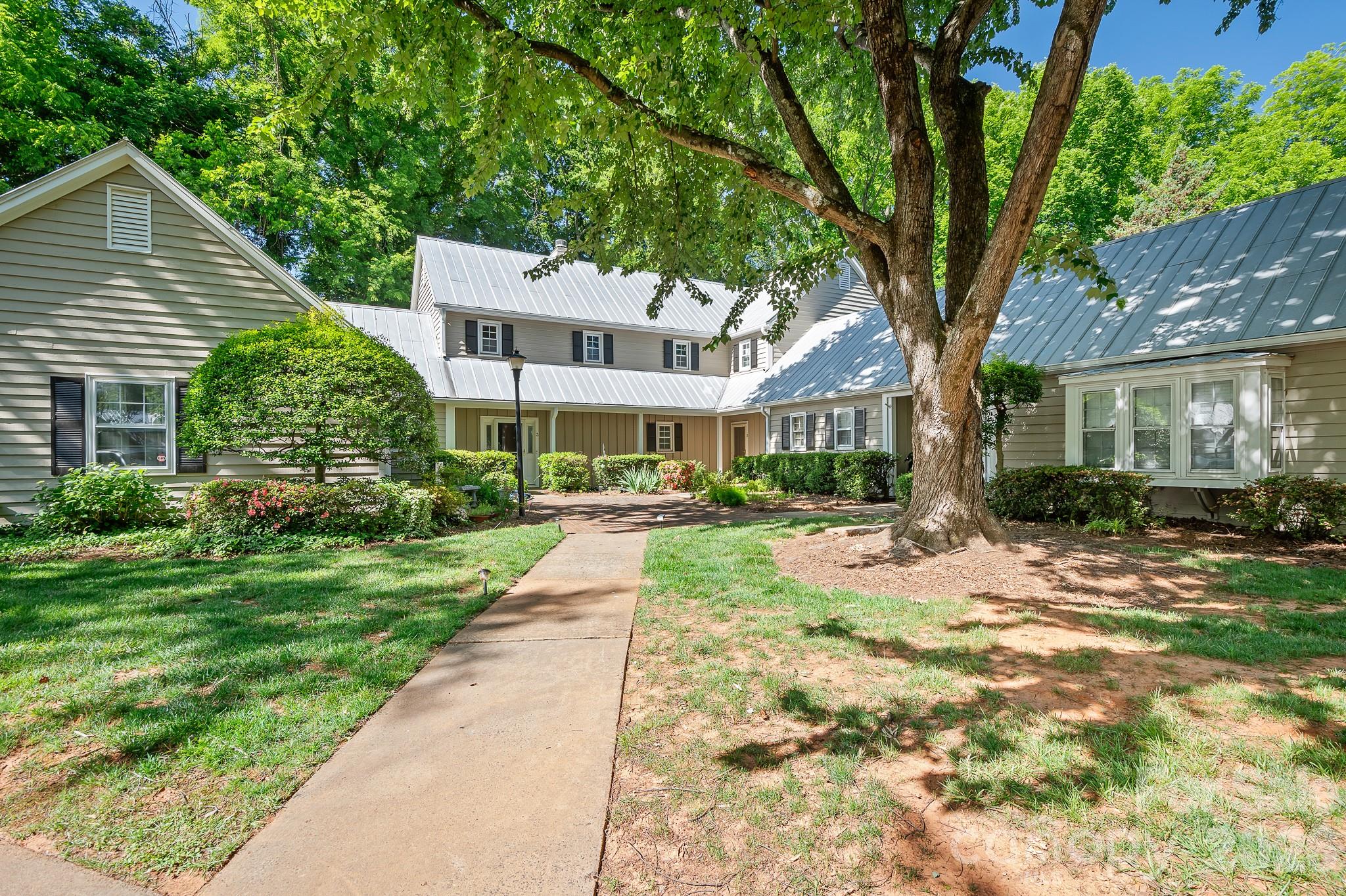 Enjoy the perfect blend of privacy and prime location in a picturesque neighborhood filled with tree-lined streets and a welcoming community pool. This delightful cottage-style condo features a secluded patio surrounded by a privacy fence, offering your own outdoor retreat. Nestled in the heart of Sedgefield, you are just moments from South End, Park Road, and Dilworth, with coffee shops, restaurants, and parks all within easy reach. Step inside to discover a living room brimming with character, complete with a cozy fireplace and elegant French doors that open to the backyard patio and fresh paint throughout. The open kitchen flows seamlessly into the dining area, with space for a breakfast bar and direct access to the patio through another set of French doors. An updated half bath graces the main level. Upstairs, unwind in the primary bedroom, where charming doors overlook the patio, and indulge in the newly renovated primary bath with a new luxurious shower, vanity, sink, & mirrors. The conveniently located hallway washer and dryer serve both bedrooms. The second bedroom offers its own en-suite bathroom, updated vanity, sink and mirror and a walk-in closet, with more charming doors framing views of the patio. The patio also has an outside storage area. Enjoy the treelined walk to the neighborhood pool.  The delightful, charming condo won't last long, it's just waiting for you to enjoy.