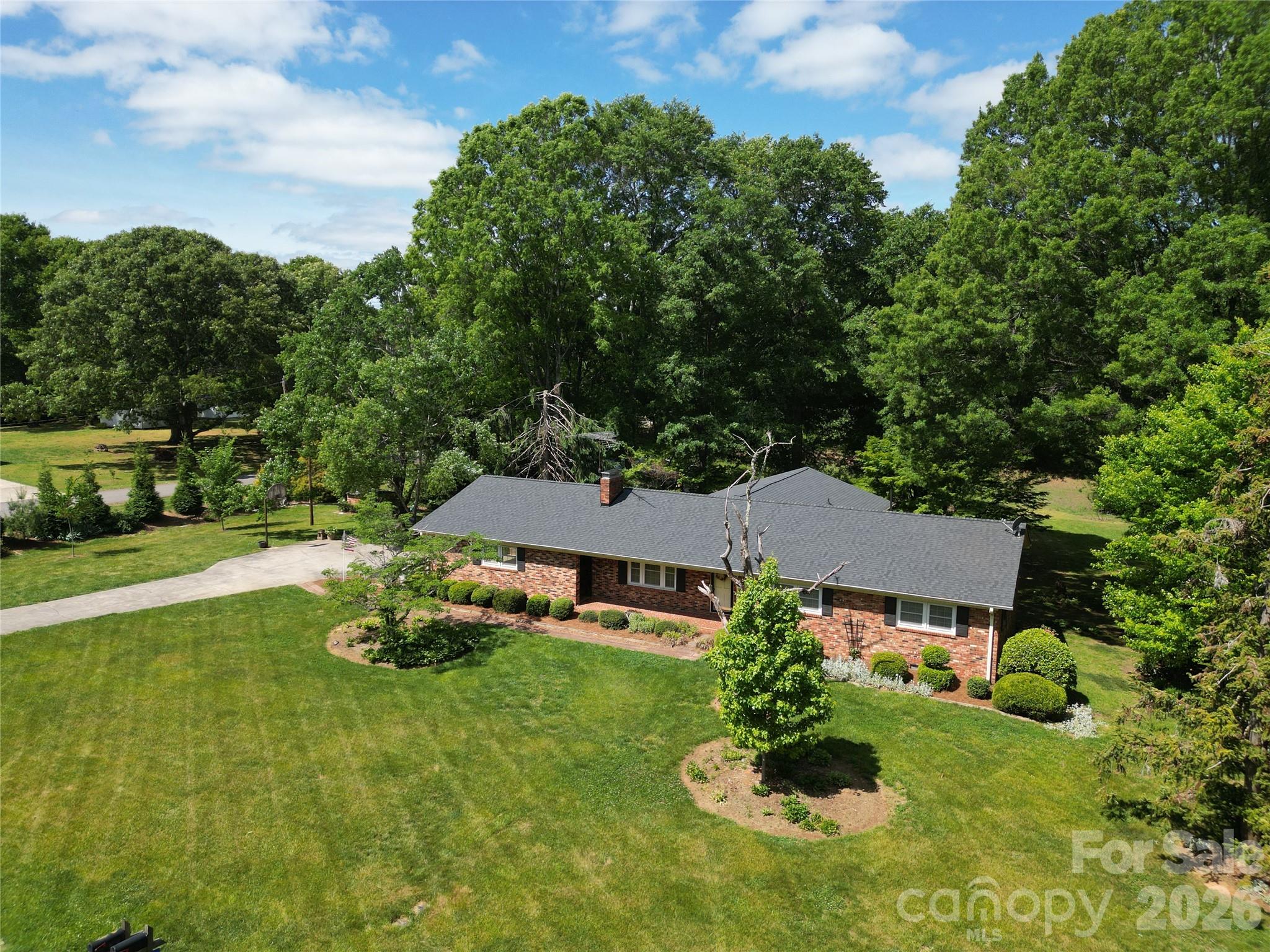 Tucked away on nearly 7 acres of private, naturally wooded land, this property offers a rare combination of space, seclusion, and flexibility just minutes from the convenience of Statesville. Surrounded by mature foliage and set back from the road, the setting delivers a quiet, retreat-like atmosphere ideal for those seeking privacy without sacrificing accessibility.

Originally built in 1972 and thoughtfully expanded in 2001, the home offers over 2,300 square feet of living space designed for both comfort and versatility. The standout feature is a spacious great room addition with vaulted ceilings and a fireplace, creating a warm and inviting central living space filled with natural light. This area flows seamlessly to an oversized rear deck, providing the perfect setting for outdoor entertaining, quiet mornings, or enjoying the peaceful natural surroundings.

The property’s 6.89 acres are a blend of cleared and wooded land, offering a balance of open usable space and privacy. The backyard features established garden areas, ideal for those looking to grow their own vegetables or create a personalized outdoor living environment. A secondary well on the property supports irrigation and landscaping needs, adding functionality for gardening enthusiasts or those seeking a more self-sufficient lifestyle.

Inside, the home is rich with character and presents an excellent opportunity for a buyer to personalize and update to their own style over time. Hardwood flooring runs through much of the home, while the layout offers flexibility for a variety of living arrangements. The unfinished basement provides additional space ideal for a workshop, storage, or future expansion based on your needs.

Recent improvements include a new roof installed in 2023, offering peace of mind and long-term value. The home is serviced by city water, with the added benefit of the private well for exterior use. With no HOA restrictions, the property provides the freedom to truly make it your own.

Whether you’re searching for a private retreat, additional space to spread out, or a property with long-term potential and flexibility, this home presents a compelling opportunity to create something truly special.