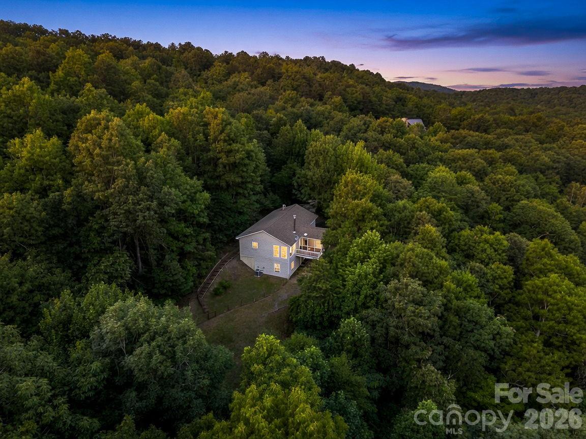 Escape to a private mountain sanctuary tucked away in the peaceful setting of High Rock Acres, just minutes from downtown Black Mountain! This home offers the ultimate retreat, completely surrounded by nature. It is an ideal setting for anyone looking to unplug, unwind, and enjoy true peace and quiet.

This home has been meticulously cared for and exceptionally well-maintained, making it a true move-in ready home. The open floorplan has lots of natural light, and the screened deck is perfect for enjoying time outside.  Inside, the home features a bright and airy open floor plan that flows seamlessly, making the space feel both expansive and connected. The wood stove in the living room is perfect for cold winter nights. There is a mountain view from the large windows, and there is potential to open this view up significantly with a little tree work.

There is a dedicated storage shed and a fully fenced dog yard, perfect for your pets to roam safely. You can enjoy the absolute privacy of mountain living without feeling isolated, as the shops, local restaurants, and charm of downtown Black Mountain are only minutes away from your front door. It is the perfect balance of a secluded natural getaway and everyday convenience. This is a great option for a primary home, or a second home with short-term rental potential.

The driveway is not steep and is in great condition. The first section of High Rock Acres Drive is currently being paved, and should be finished in the next few weeks. The rest of the road is well-maintained with a voluntary road maintenance agreement. New HVAC in 2025.
