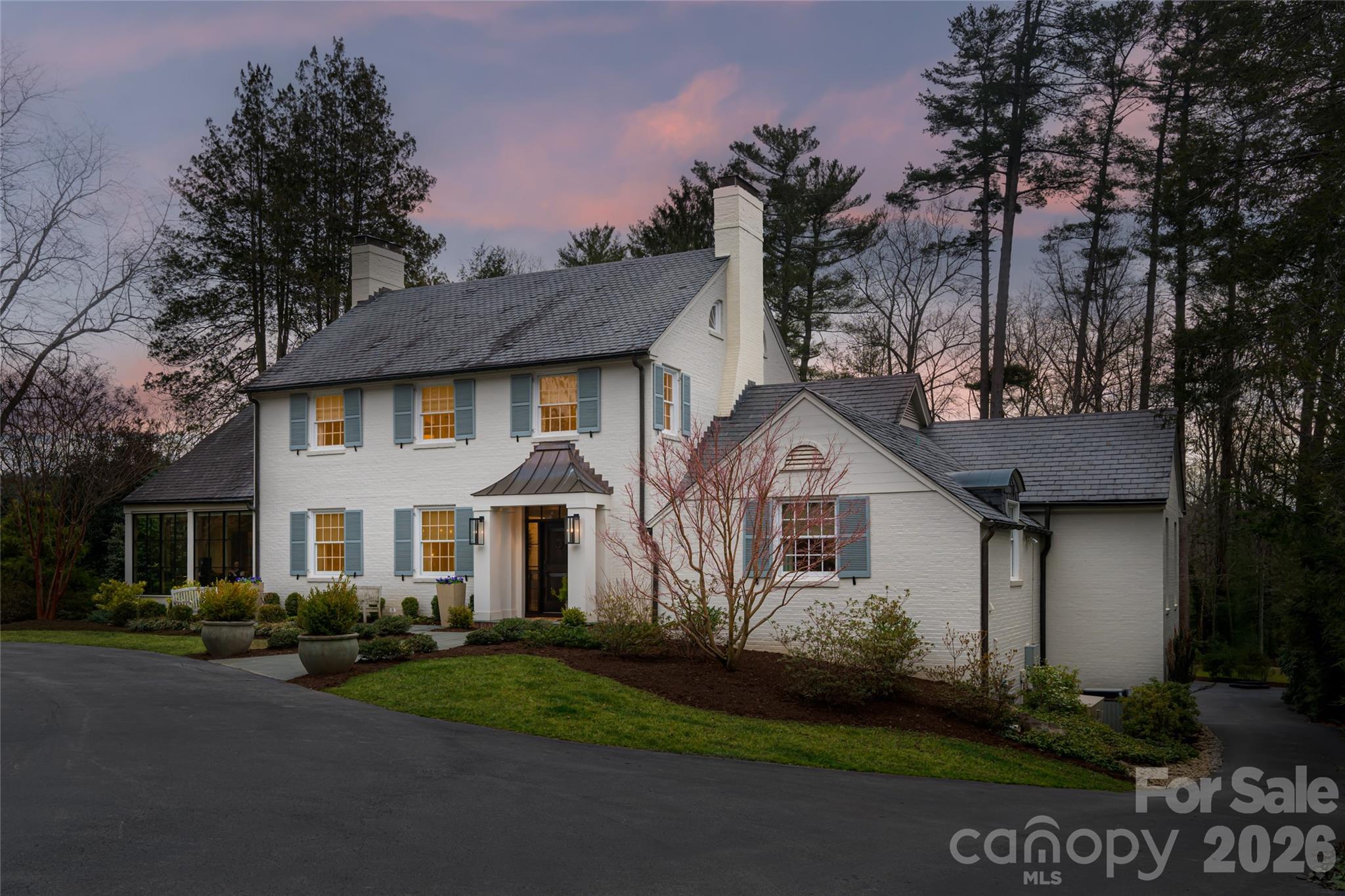 From the moment you enter through the front door, 28 Hilltop Road captivates with its warm coastal aesthetic and beautifully layered finishes, creating an atmosphere of relaxed sophistication. A dramatic whole-home renovation, completed by Preish Construction (2019-2021), has transformed the residence into a thoughtfully crafted, designer-appointed sanctuary where architectural character and modern comfort coexist seamlessly. 

Walls were opened to create an expansive, flowing layout that moves effortlessly from front entry into the primary living spaces. This open gathering environment, anchored by the spacious kitchen, forms the heart of the home and is infused with a quiet, refined ease. Wide-plank oak hardwoods establish an organic palette carried through the cabinetry, doors and fine detailing throughout. The gourmet kitchen and breakfast area, fully open to the living room, continue the home’s relaxed, designer-inspired style. Custom reeded cabinetry by Forest Millwork introduces rich texture and depth, while the dramatic 12-foot marble island makes a striking statement and naturally gathers family and guests. A herringbone marble pattern extends across the backsplash and kitchen window wall, while a professional-grade appliance suite by Wolf and Sub-Zero completes the space. Sliding doors open to an expansive covered rear patio, an effortless extension of living space and a setting for enjoying the private backyard and Western North Carolina’s four-season lifestyle. 

The main-level primary suite unfolds as a serene private sanctuary, distinguished by a striking wood-finished domed ceiling with beams, a travertine-encased gas fireplace, and a gracious walk-in closet. Echoing the suite’s tranquil tone, the spa-inspired bath offers a soaking tub, dual vanities, refined lighting and a Walker Zanger-clad walk-in shower with rain showerhead. For everyday ease, the laundry room, finished with custom cabinetry, marble countertops and farmhouse sink, was thoughtfully relocated to the primary suite. 

The dining room adds another layer of coastal character with shiplap walls and natural ceiling beams, while a marble-encased fireplace brings refined warmth for intimate gatherings. 

Also on the main level, a light-filled office/den was created by re-imagining the original sunroom. Raised floors and new floor-to-ceiling windows introduce abundant light, while handsome millwork, built-ins, and a converted gas-log fireplace create an inviting and beautifully composed workspace. 

Upstairs are three private en-suite bedrooms, tastefully updated while preserving the original skinny-oak hardwood floors. Each offers a renovated bath with custom tile, cabinetry and heated floors. A smaller bedroom or flexible bonus room provides additional versatility. 

Designed for flexibility, the finished lower level provides media, recreation and guest living quarters with a secondary living area, bar and fireplace. A spacious, climate-controlled gym has been created in the two-car garage, while a separate third garage bay remains intact, allowing easy conversion back to full three-car garage parking depending upon your needs. 

Ideally located near Greenwood Park, Carolina Day School and Biltmore Forest Country Club (an invitation-only club) all within an easy walk or bike ride. Gracefully set back on just over an acre with a circular drive approach, this residence stands as a Biltmore Forest gem in one of Asheville’s storied and distinctive neighborhoods.