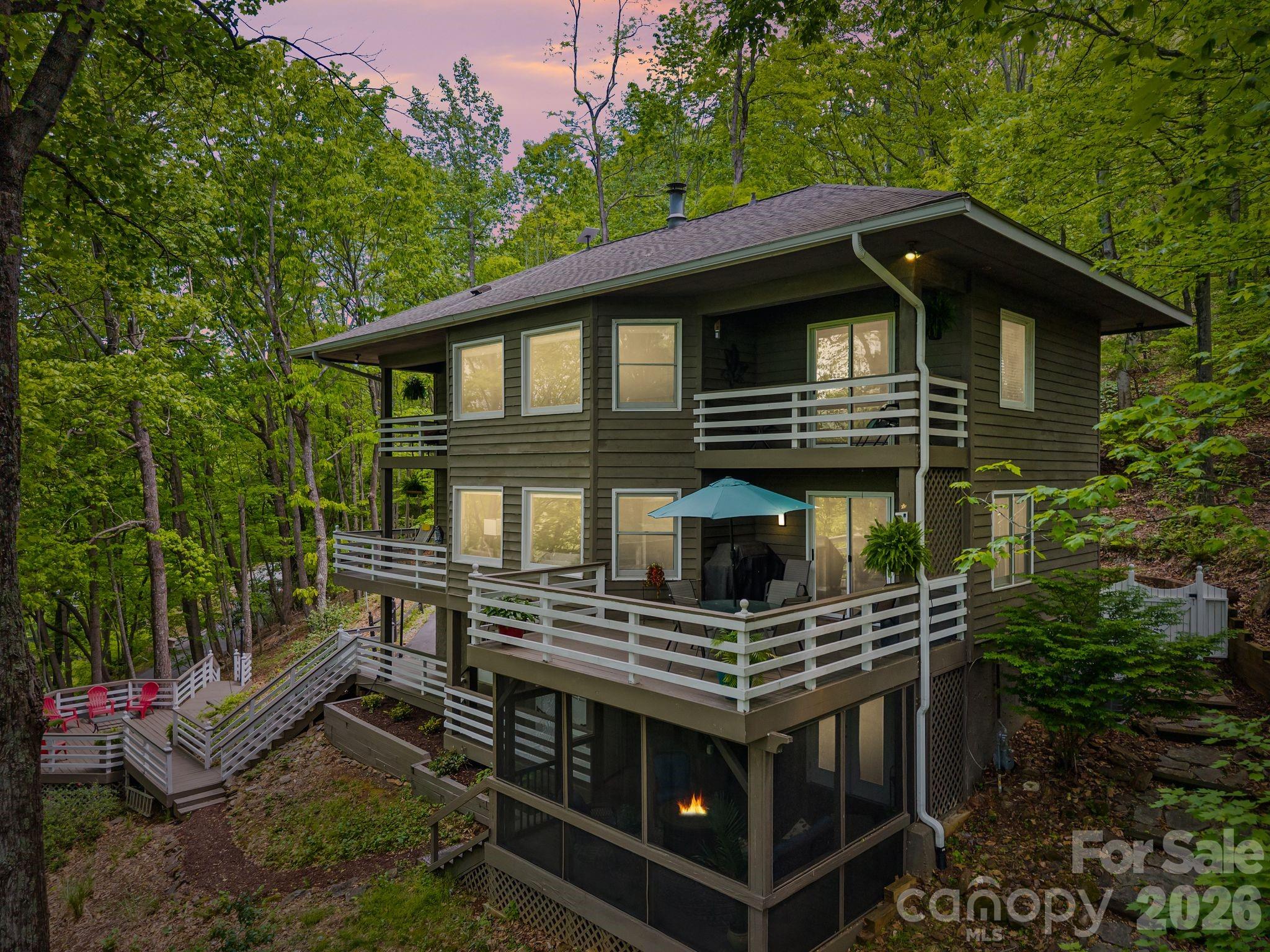 Nestled in a canopy of trees with stunning western views of Pisgah National Forest and spectacular sunsets, this 3-bedroom, 3-bath home offers 2,500 square feet of thoughtfully designed living space in the coveted gated community of High Vista. An abundance of windows floods the interior with natural light and keeps the surrounding treeline and mountain views front and center throughout the home. Decks on all three levels provide multiple outdoor living areas to take in the scenery year-round, complemented by a screened porch on the lower level which seamlessly expands the lower level living space. The renovated primary bathroom is a true retreat, featuring a soaking tub and an oversized shower and a wall of windows so you never miss a sunset. A bonus room offers extra space for a home office, gym, or media room, and a 2-car garage rounds out the practicalities. Kitchen appliances were all replaced in 2025. High Vista residents enjoy access to an optional pool and recreation membership, with Chestnut Mountain Golf Club located within the community. This is refined mountain living at its finest. Visit www.highvistamillsriver.com for additional community info.