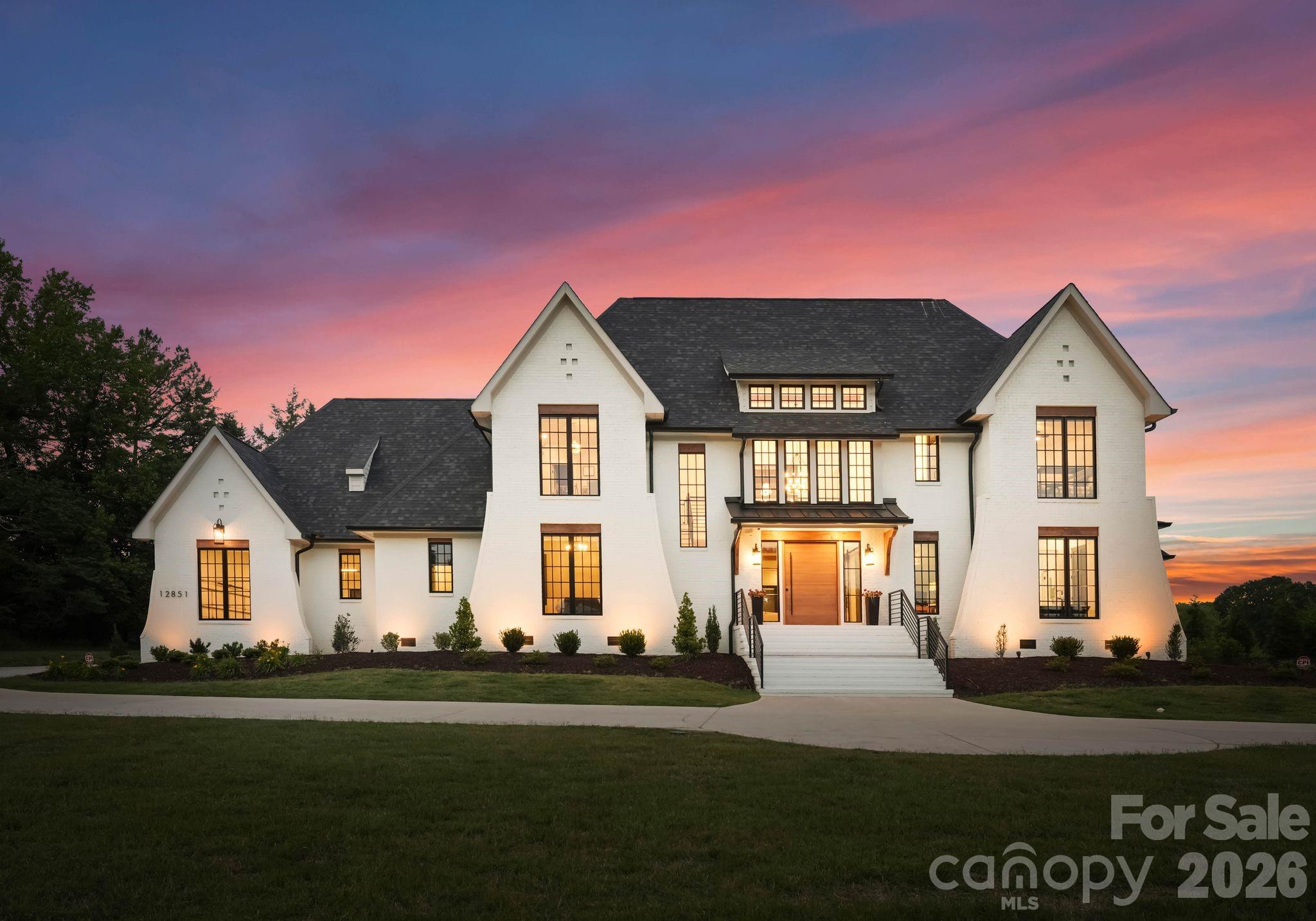 Designed for those who want every day to feel like an escape, this extraordinary custom estate overlooking tranquil pond views in the heart of Davidson delivers a rare blend of architectural sophistication, resort-inspired amenities, and elevated everyday living. Completed in 2024 and set on 1.33 pristine acres, the residence offers an exceptional lifestyle just moments from Davidson College, downtown Davidson’s beloved restaurants, boutiques, and everyday conveniences. Created to rival the experience of a private luxury resort, the outdoor living spaces are nothing short of spectacular. Framed by breathtaking sunset views and serene water vistas, the backyard retreat features a heated saltwater pool and spa, expansive fenced AstroTurf lawn, multiple lounging and entertaining areas, and a covered outdoor living pavilion complete with a fireplace and fully equipped outdoor kitchen offering the perfect setting for both intimate evenings and large-scale entertaining. Inside, refined craftsmanship and curated designer finishes define every space. Soaring ceilings, dramatic wood and metal beam accents, expansive sliding glass doors, oversized windows, and layered architectural details create a warm yet striking modern aesthetic throughout. The chef’s kitchen is equally impressive, showcasing premium stainless steel appliances, custom cabinetry, oversized island, and seamless open-concept gathering spaces thoughtfully designed for effortless entertaining and everyday luxury. The main-level primary suite serves as a private sanctuary featuring a spa inspired bath and expansive custom his and hers dressing rooms. Upstairs, three additional bedrooms are complemented by exceptional flex spaces including a recreation room with entertaining bar, bonus/media room, exercise studio, and custom bunk room offering remarkable versatility without compromising style or comfort. From its commanding presence and breathtaking backdrop to its meticulously curated interiors and resort-inspired grounds, this exceptional Davidson residence was thoughtfully designed to elevate every aspect of modern luxury living.
