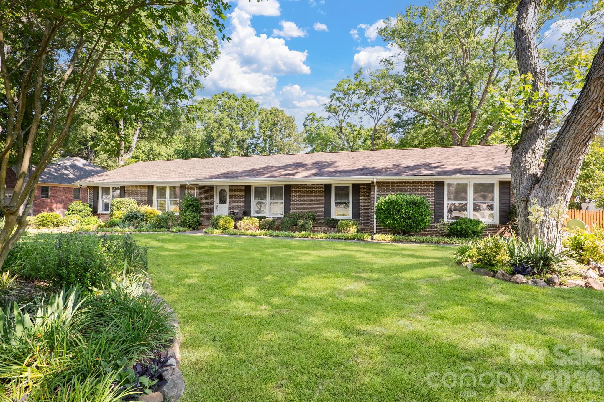 Charming ranch home in an established neighborhood with a fantastic location just minutes from the highway and convenient to University of North Carolina at Charlotte, PNC Music Pavilion, and Concord Mills. This well-maintained home features a spacious great room with abundant natural light and a cozy wood-burning fireplace, a country kitchen with stainless steel appliances, tile backsplash, ample cabinetry, and breakfast area, plus a versatile dining room with French doors ideal for a home office. The converted garage offers additional flex space with endless possibilities. Enjoy the large level backyard with mature fruit trees, lush landscaping, plenty of sunshine for gardening, and a storage shed for lawn equipment. All bedrooms include ceiling fans, and the home is truly move-in ready! Refrigerator, Washer and Dryer to convey.