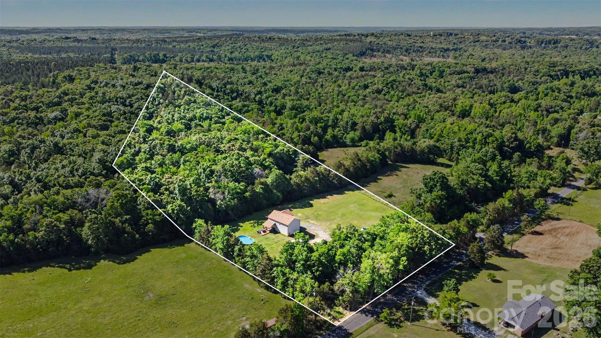 Beautifully maintained home nestled on 6.3 PRIVATE ACRES, surrounded by adjoining 6 and 18-acre parcels for added seclusion and tranquility. Mature trees and established landscaping create a peaceful setting while still offering convenient access to York, Clover, and Charlotte. Inside, the bright open-concept layout is warm and inviting, featuring a spacious family room, dining area, and stunning kitchen with granite countertops, center island, custom cabinetry, subway tile backsplash, and oversized walk-in pantry. Upstairs, the generous primary suite features a deep walk-in closet and bathroom with private water closet and walk-in shower. Three additional bedrooms provide ample storage, along with a conveniently located upstairs laundry room and linen closet. Step outside to the large covered deck perfect for entertaining and grilling overlooking the spacious backyard and luxurious  oversized above-ground pool.  The property also offers exceptional storage and workspace with an attached 2-car garage, detached garage/workshop and a 30-amp hookup for parking an RV. Enjoy the best of country living with no HOA while remaining just minutes from the quaint village of York, shopping, dining, and outdoor recreation. Low county taxes and transferable structural warranty with approximately 7 years remaining add additional peace of mind. Come make this beautiful serene home yours!