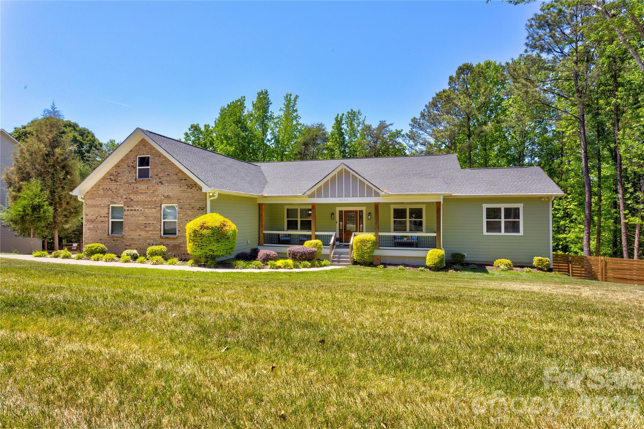 Discover this stunning, practically new (built in 2021) 5-bedroom, 4.5-bath ranch-style residence, perfectly situated on a sprawling, nearly ¾-acre lot in an established neighborhood with NO HOA.
Step inside the inviting, open-concept home designed for effortless entertaining. The chef-inspired gourmet kitchen is anchored by a large quartz island featuring a gas cooktop and built-in microwave, flowing seamlessly into the dining and breakfast areas. The adjacent family room boast a cathedral ceiling with exposed beams, a cozy fireplace, and custom built-ins. Enjoy access to the back deck directly from this central gathering space. The main level is completed by a split-bedroom  floor plan with 2 full baths, ensuring ultimate privacy.The secluded main floor Primary Suite is a luxurious retreat with cathedral ceilings. Its opulent primary bath features elegant tile floors, a freestanding soaking tub, and a huge walk-in tiled shower. A secondary Primary Suite is located on the lower level, offering flexible living arrangements.The full, walk-out basement is designed as an entertainment hub, featuring a large family room that flows onto the stamped concrete patio. The patio is equipped with a luxurious heated Four Winds swim spa, perfect for year-round swimming or relaxing. This level also includes a versatile bonus room that can be utilized as a playroom, large office, or dedicated gym.Relax on the classic rocking chair front porch or the back deck overlooking the downstairs patio. The private backyard is fully enclosed with a custom wood fence (featuring three gates for easy access) and offers a serene view of mature hardwood trees and a beautiful tree canopy. The property provides extensive parking with a 2-car garage on the main level and a massive, oversized garage/storage area in the basement.This home offers peace of mind with maintenance-free elements including Trex decking, GutterGuard, a stamped concrete patio, and transferable termite and HVAC bonds.Enjoy quick access to everything, as you are less than five minutes from I-485, major shopping, dining, and local hospitals. Don't miss this rare opportunity for luxury, acreage, and convenience without the restrictions of an HOA.