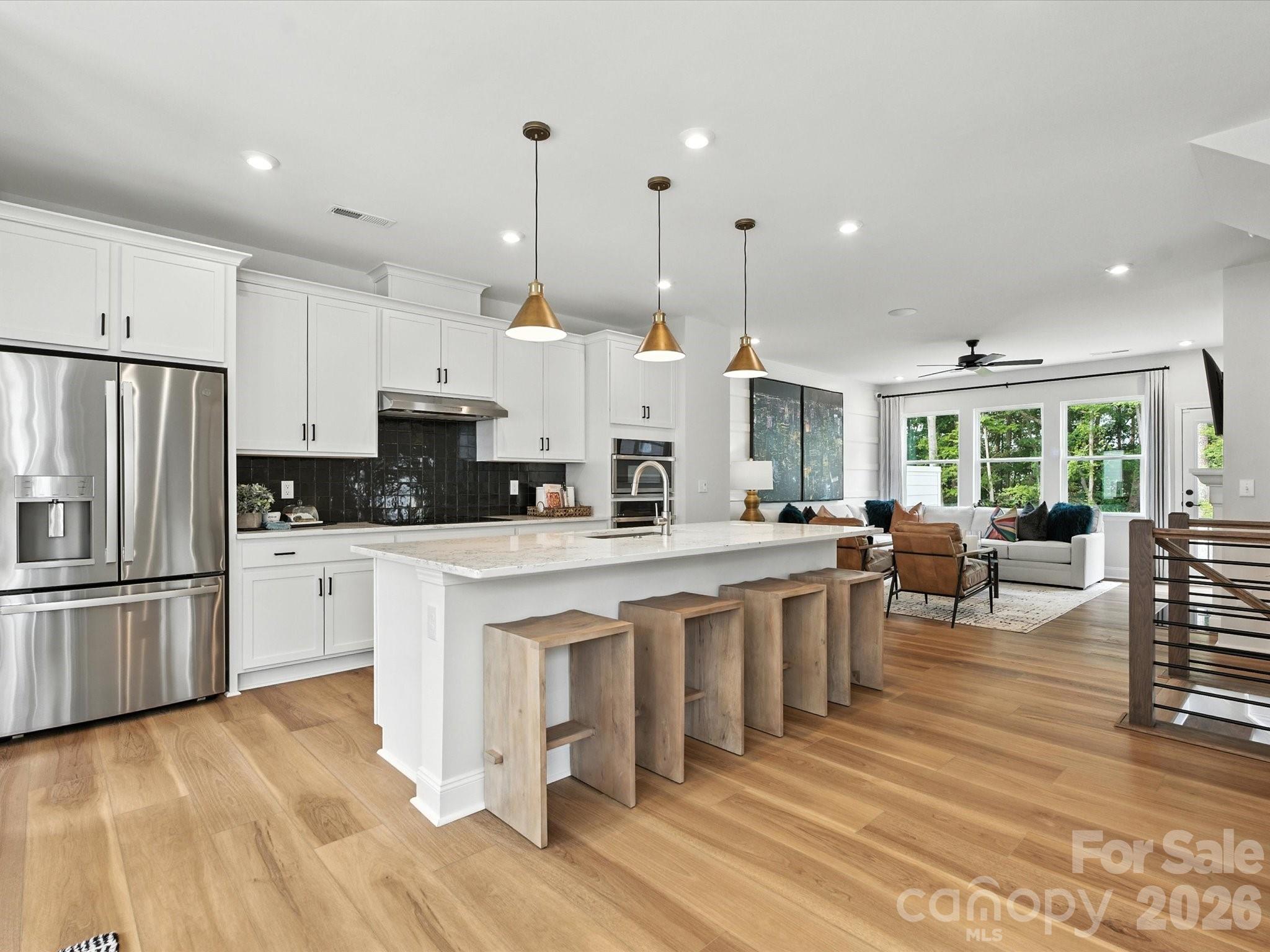 This fully furnished Beau model home at Archer Row is available for purchase, your opportunity to own a designer-curated end-unit townhome with upgrade, finish, and furnishing already in place. Spanning three stories and 2,113 square feet, this 4-bedroom, 3.5-bath home with a front-load 2-bay garage is designed for the way you actually live. The first floor welcomes you with a private bedroom and full bath featuring a tiled walk-in shower, plus access to a covered outdoor living space. Oak box stairs with open-rail black balusters lead to the heart of the home on the second floor, where an open-concept great room anchored by a built-in 36" electric fireplace and filled with natural light flows into a stunning gourmet kitchen. White cabinetry paired with black hardware, Arabescato Twilight white quartz countertops, and a black 4x4 Zellige Neo Carbone backsplash create a bold, sophisticated palette, complemented by a large single-bowl stainless steel sink, GE Profile 36" electric cooktop, single oven, Advantium oven, under-cabinet hood, and a counter-depth French-door refrigerator, all in stainless steel. A second outdoor living space rounds out the second floor. Upstairs, the primary suite impresses with tray ceilings, a tiled walk-in shower, dual vanity with warm brown cabinetry and drawers, and direct access to the walk-in closet. Two additional bedrooms, a shared bath, and a laundry closet with the GE Front Load Electric Laundry Set in Sapphire Blue complete the third floor. Designer furnishings throughout are included with purchase, making this a truly move-in ready opportunity. All of this just minutes from I-77, the airport, and Uptown Charlotte.