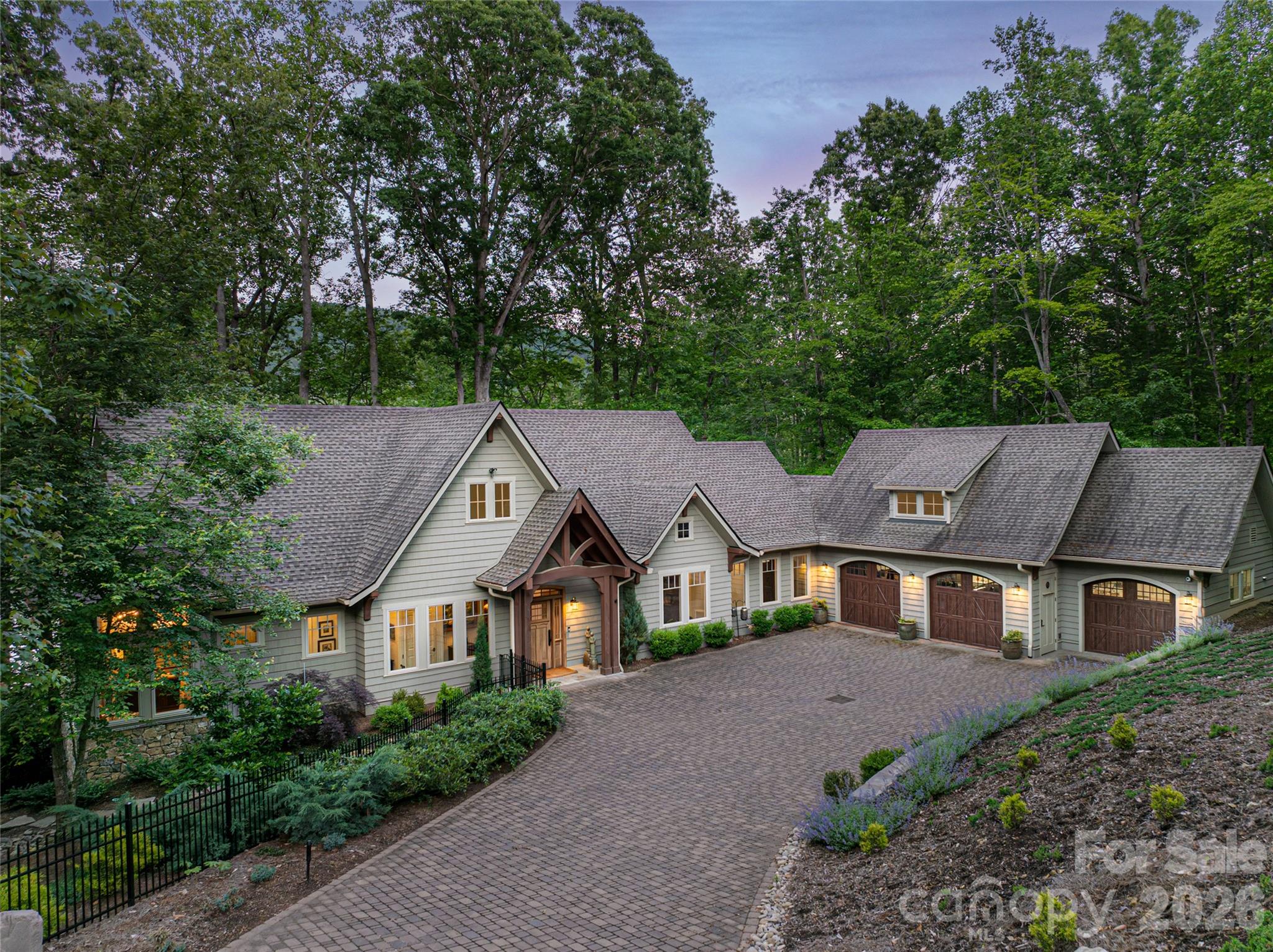 Lakefront living overlooking the water, where modern elegance meets timeless design and every detail has been thoughtfully curated for refined living. Nearly every room captures tranquil water views and breathtaking sunrises, creating a daily connection to the natural beauty of Enka Lake. Beyond the striking setting, this exceptional residence delivers a seamless blend of luxury, comfort and effortless functionality. Expansive living spaces, soaring ceilings and walls of windows fill the home with natural light, creating an atmosphere that feels sophisticated and inviting. Thoughtfully designed for everyday living and entertaining alike, the floor plan offers an ideal balance of openness and privacy. At the center of the home, the chef’s kitchen is stunning and highly functional, featuring granite and quartzite countertops, premium appliances, custom cabinetry, and generous prep and gathering spaces. The kitchen flows naturally into the main living and dining areas, as well as a beautifully appointed office with rich wood built-ins, ideal for remote work, reading or quiet retreat. The main-level primary suite is a luxurious sanctuary overlooking the lake, complete with spa-inspired finishes, spacious closets and a calming ambiance designed for relaxation. Additional guest bedrooms and flexible living areas provide ample room for family and visitors, while exceptional storage throughout the home enhances convenience and organization. Modern features, including geothermal heating and provisions for a future elevator, reflect the home’s commitment to efficiency, comfort and long-term livability. Outdoor living is equally impressive. Expansive porches and patios create inviting spaces for morning coffee, sunset gatherings or simply enjoying the peaceful waterfront surroundings. Whether entertaining guests or unwinding after a busy day, the connection between indoor and outdoor living is effortless and inspiring. Within the gated community of Biltmore Lake, residents enjoy private streets, beautifully maintained grounds, and an unmatched lifestyle centered around recreation and connection. Community amenities include a 2.2-mile lake trail, clubhouse, playgrounds, tennis and basketball courts, boating, paddleboarding, canoeing and fishing, all just moments from your door. Despite its tranquil setting, the home is conveniently only minutes from downtown Asheville, where acclaimed restaurants, art galleries, live music and vibrant cultural experiences await. Outdoor enthusiasts will also appreciate proximity to the Blue Ridge Parkway, Pisgah National Forest and the French Broad River. Offering the rare combination of refined craftsmanship, modern amenities and an extraordinary waterfront setting, this like-new residence captures the best of luxury lakefront living in one of Western North Carolina’s sought-after communities.