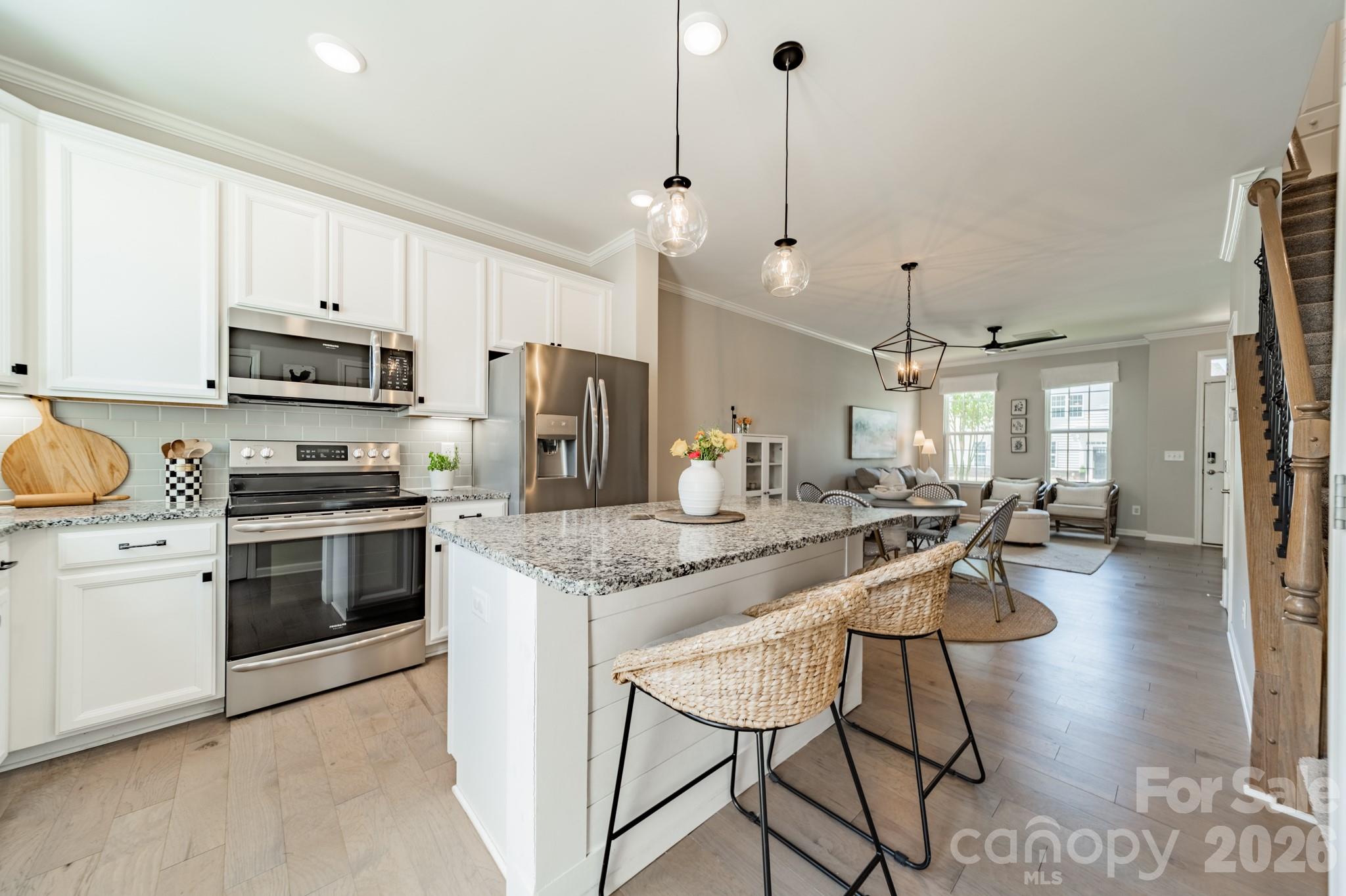 Beautifully finished townhome with two assigned parking spaces directly by your front door. Waters Edge is a newer townhome community in an amazing location across from the new CaroMont Hospital, next door to the McGill Family Recreation Center and along the shores of Lake Wylie. Just across the highway from the quaint Town of Belmont NC with its city park, restaurants, shops and festivals, this 2018 built townhome in Waters Edge provides a perfect option for maintenance-free living. Located on a level lot, this unit features a fenced patio courtyard with a storage space too. When the weather is warm, enjoy the community pool a very short walk down the street from your home. So much to love about this property! Inside this well maintained townhome, you will find an open floor plan on the main level. Current finishes are featured with white cabinetry, beige-gray solid surface flooring throughout the main level, granite counters, and black metal stair pickets. A pantry closet and convenient half bath are also located on the main level. This floor plan is so convenient. Lots of natural light in this home from the front and rear windows/door bring a smile every day! Open the rear door to enjoy even more sunshine in your outdoor living space. Ample cabinets along with a generously sized island make cooking and dining a joy. Plus the dining area can be used for sit-down meals or working from home space. The living room has a natural space for your media which you can view from the generously sized area for seating furniture. The main level also features an interior walk-in closet for storing coats and anything else you need to put away. Walk up the stairs and you will find two generously sized bedrooms with two full baths. Plush carpet warms your feet every morning and night. A sizable closet in the primary bedroom provides ample space for your shoes and clothes. A walk-in shower in the primary bath is also generously sized and features a tiled surround plus tile floor.  The secondary full bath also features a tiled tub surround plus tiled floor. The laundry closet is also located upstairs which is so convenient being on the same level as the bedrooms. The seller is leaving the washer, dryer and the kitchen refrigerator as well - love it! Please come take a look at this beautiful townhome - between the finishes and the location, you can't beat this opportunity!
